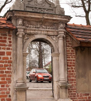 Zdjęcie nr 17: Kościół położony na południe od rynku, na placu otoczonym kamiennym murem z dwiema bramkami od zachodu i północy oraz bramką od południa. Kościół jednonawowy, dwuprzęsłowy, z węższym, niższym dwuprzęsłowym prezbiterium zamkniętym pięciobocznie. Do prezbiterium przylegają dwa aneksy, od północy dawna zakrystia (obecnie kaplica świętych Męczennic), zamknięta od wschodu dwubocznie, mająca w narożu z korpusem wieżyczkę schodową, a od południa zakrystia nowa, na planie prostokąta. Do nawy przylegają dwie kaplice: od północy kaplica Lubomirskich, założona na rzucie kwadratu, nakryta kopułą, a od południa kaplica Branickich, także na rzucie kwadratu z kopułą. Przy korpusie od zachodu piętrowa kruchta, pierwotnie otwarta w przyziemiu od północy, zachodu i południa ostrołukowymi arkadami. Arkada tęczy ostrołukowa. Sklepienie prezbiterium, zakrystii i obu kondygnacjach kruchty krzyżowo-żebrowe, w korpusie, pierwotnie trójprzęsłowym, pierwotnie sklepienie o polach trójkątnych z trójpromieniem, wsparte na dwóch dziesięciobocznych filarach, obecnie kolebkowo z lunetami. Żebra w prezbiterium i zakrystii o profilu żłobkowym, w kruchcie - gruszkowym. W prezbiterium służki cylindryczne, nadwieszone na oplecionych liśćmi wspornikach oraz rzeźbione zworniki z przedstawieniem Głowy Chrystusa i motywami roślinnymi. Ściany rozczłonkowane wykonanymi w czarnego marmuru arkadami, zamkniętymi łukiem półkolistymi. Okna ostrołukowe , obustronnie rozglifione z krzyżowym laskowaniem, w ścianie północnym prezbiterium ślepe. Kościół opięty przyporami. Elewacje na cokole, z profilowanymi gzymsami cokołowymi, kapnikowym i koronującym. Szczyty zwieńczone kwiatonami, z których zachodnie z krzyżem. Portale kamienne, ostrołukowe: zachodni profilowany, z ażurowym maswerkiem; drugi w prezbiterium do zakrystii, profilowany; trzeci do wieżyczki schodowej.