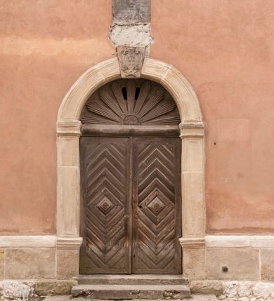 Zdjęcie nr 18: Kościół położony na południe od rynku, na placu otoczonym kamiennym murem z dwiema bramkami od zachodu i północy oraz bramką od południa. Kościół jednonawowy, dwuprzęsłowy, z węższym, niższym dwuprzęsłowym prezbiterium zamkniętym pięciobocznie. Do prezbiterium przylegają dwa aneksy, od północy dawna zakrystia (obecnie kaplica świętych Męczennic), zamknięta od wschodu dwubocznie, mająca w narożu z korpusem wieżyczkę schodową, a od południa zakrystia nowa, na planie prostokąta. Do nawy przylegają dwie kaplice: od północy kaplica Lubomirskich, założona na rzucie kwadratu, nakryta kopułą, a od południa kaplica Branickich, także na rzucie kwadratu z kopułą. Przy korpusie od zachodu piętrowa kruchta, pierwotnie otwarta w przyziemiu od północy, zachodu i południa ostrołukowymi arkadami. Arkada tęczy ostrołukowa. Sklepienie prezbiterium, zakrystii i obu kondygnacjach kruchty krzyżowo-żebrowe, w korpusie, pierwotnie trójprzęsłowym, pierwotnie sklepienie o polach trójkątnych z trójpromieniem, wsparte na dwóch dziesięciobocznych filarach, obecnie kolebkowo z lunetami. Żebra w prezbiterium i zakrystii o profilu żłobkowym, w kruchcie - gruszkowym. W prezbiterium służki cylindryczne, nadwieszone na oplecionych liśćmi wspornikach oraz rzeźbione zworniki z przedstawieniem Głowy Chrystusa i motywami roślinnymi. Ściany rozczłonkowane wykonanymi w czarnego marmuru arkadami, zamkniętymi łukiem półkolistymi. Okna ostrołukowe , obustronnie rozglifione z krzyżowym laskowaniem, w ścianie północnym prezbiterium ślepe. Kościół opięty przyporami. Elewacje na cokole, z profilowanymi gzymsami cokołowymi, kapnikowym i koronującym. Szczyty zwieńczone kwiatonami, z których zachodnie z krzyżem. Portale kamienne, ostrołukowe: zachodni profilowany, z ażurowym maswerkiem; drugi w prezbiterium do zakrystii, profilowany; trzeci do wieżyczki schodowej.