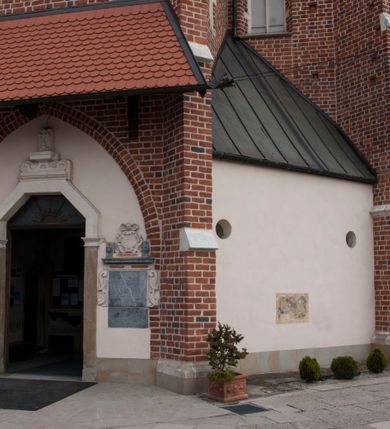 Zdjęcie nr 16: Kościół położony na południe od rynku, na placu otoczonym kamiennym murem z dwiema bramkami od zachodu i północy oraz bramką od południa. Kościół jednonawowy, dwuprzęsłowy, z węższym, niższym dwuprzęsłowym prezbiterium zamkniętym pięciobocznie. Do prezbiterium przylegają dwa aneksy, od północy dawna zakrystia (obecnie kaplica świętych Męczennic), zamknięta od wschodu dwubocznie, mająca w narożu z korpusem wieżyczkę schodową, a od południa zakrystia nowa, na planie prostokąta. Do nawy przylegają dwie kaplice: od północy kaplica Lubomirskich, założona na rzucie kwadratu, nakryta kopułą, a od południa kaplica Branickich, także na rzucie kwadratu z kopułą. Przy korpusie od zachodu piętrowa kruchta, pierwotnie otwarta w przyziemiu od północy, zachodu i południa ostrołukowymi arkadami. Arkada tęczy ostrołukowa. Sklepienie prezbiterium, zakrystii i obu kondygnacjach kruchty krzyżowo-żebrowe, w korpusie, pierwotnie trójprzęsłowym, pierwotnie sklepienie o polach trójkątnych z trójpromieniem, wsparte na dwóch dziesięciobocznych filarach, obecnie kolebkowo z lunetami. Żebra w prezbiterium i zakrystii o profilu żłobkowym, w kruchcie - gruszkowym. W prezbiterium służki cylindryczne, nadwieszone na oplecionych liśćmi wspornikach oraz rzeźbione zworniki z przedstawieniem Głowy Chrystusa i motywami roślinnymi. Ściany rozczłonkowane wykonanymi w czarnego marmuru arkadami, zamkniętymi łukiem półkolistymi. Okna ostrołukowe , obustronnie rozglifione z krzyżowym laskowaniem, w ścianie północnym prezbiterium ślepe. Kościół opięty przyporami. Elewacje na cokole, z profilowanymi gzymsami cokołowymi, kapnikowym i koronującym. Szczyty zwieńczone kwiatonami, z których zachodnie z krzyżem. Portale kamienne, ostrołukowe: zachodni profilowany, z ażurowym maswerkiem; drugi w prezbiterium do zakrystii, profilowany; trzeci do wieżyczki schodowej.