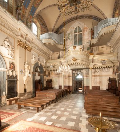 Zdjęcie nr 26: Kościół położony na południe od rynku, na placu otoczonym kamiennym murem z dwiema bramkami od zachodu i północy oraz bramką od południa. Kościół jednonawowy, dwuprzęsłowy, z węższym, niższym dwuprzęsłowym prezbiterium zamkniętym pięciobocznie. Do prezbiterium przylegają dwa aneksy, od północy dawna zakrystia (obecnie kaplica świętych Męczennic), zamknięta od wschodu dwubocznie, mająca w narożu z korpusem wieżyczkę schodową, a od południa zakrystia nowa, na planie prostokąta. Do nawy przylegają dwie kaplice: od północy kaplica Lubomirskich, założona na rzucie kwadratu, nakryta kopułą, a od południa kaplica Branickich, także na rzucie kwadratu z kopułą. Przy korpusie od zachodu piętrowa kruchta, pierwotnie otwarta w przyziemiu od północy, zachodu i południa ostrołukowymi arkadami. Arkada tęczy ostrołukowa. Sklepienie prezbiterium, zakrystii i obu kondygnacjach kruchty krzyżowo-żebrowe, w korpusie, pierwotnie trójprzęsłowym, pierwotnie sklepienie o polach trójkątnych z trójpromieniem, wsparte na dwóch dziesięciobocznych filarach, obecnie kolebkowo z lunetami. Żebra w prezbiterium i zakrystii o profilu żłobkowym, w kruchcie - gruszkowym. W prezbiterium służki cylindryczne, nadwieszone na oplecionych liśćmi wspornikach oraz rzeźbione zworniki z przedstawieniem Głowy Chrystusa i motywami roślinnymi. Ściany rozczłonkowane wykonanymi w czarnego marmuru arkadami, zamkniętymi łukiem półkolistymi. Okna ostrołukowe , obustronnie rozglifione z krzyżowym laskowaniem, w ścianie północnym prezbiterium ślepe. Kościół opięty przyporami. Elewacje na cokole, z profilowanymi gzymsami cokołowymi, kapnikowym i koronującym. Szczyty zwieńczone kwiatonami, z których zachodnie z krzyżem. Portale kamienne, ostrołukowe: zachodni profilowany, z ażurowym maswerkiem; drugi w prezbiterium do zakrystii, profilowany; trzeci do wieżyczki schodowej.