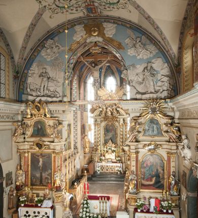 Zdjęcie nr 30: Kościół położony na południe od rynku, na placu otoczonym kamiennym murem z dwiema bramkami od zachodu i północy oraz bramką od południa. Kościół jednonawowy, dwuprzęsłowy, z węższym, niższym dwuprzęsłowym prezbiterium zamkniętym pięciobocznie. Do prezbiterium przylegają dwa aneksy, od północy dawna zakrystia (obecnie kaplica świętych Męczennic), zamknięta od wschodu dwubocznie, mająca w narożu z korpusem wieżyczkę schodową, a od południa zakrystia nowa, na planie prostokąta. Do nawy przylegają dwie kaplice: od północy kaplica Lubomirskich, założona na rzucie kwadratu, nakryta kopułą, a od południa kaplica Branickich, także na rzucie kwadratu z kopułą. Przy korpusie od zachodu piętrowa kruchta, pierwotnie otwarta w przyziemiu od północy, zachodu i południa ostrołukowymi arkadami. Arkada tęczy ostrołukowa. Sklepienie prezbiterium, zakrystii i obu kondygnacjach kruchty krzyżowo-żebrowe, w korpusie, pierwotnie trójprzęsłowym, pierwotnie sklepienie o polach trójkątnych z trójpromieniem, wsparte na dwóch dziesięciobocznych filarach, obecnie kolebkowo z lunetami. Żebra w prezbiterium i zakrystii o profilu żłobkowym, w kruchcie - gruszkowym. W prezbiterium służki cylindryczne, nadwieszone na oplecionych liśćmi wspornikach oraz rzeźbione zworniki z przedstawieniem Głowy Chrystusa i motywami roślinnymi. Ściany rozczłonkowane wykonanymi w czarnego marmuru arkadami, zamkniętymi łukiem półkolistymi. Okna ostrołukowe , obustronnie rozglifione z krzyżowym laskowaniem, w ścianie północnym prezbiterium ślepe. Kościół opięty przyporami. Elewacje na cokole, z profilowanymi gzymsami cokołowymi, kapnikowym i koronującym. Szczyty zwieńczone kwiatonami, z których zachodnie z krzyżem. Portale kamienne, ostrołukowe: zachodni profilowany, z ażurowym maswerkiem; drugi w prezbiterium do zakrystii, profilowany; trzeci do wieżyczki schodowej.