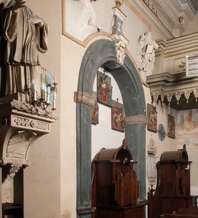 Zdjęcie nr 55: Kościół położony na południe od rynku, na placu otoczonym kamiennym murem z dwiema bramkami od zachodu i północy oraz bramką od południa. Kościół jednonawowy, dwuprzęsłowy, z węższym, niższym dwuprzęsłowym prezbiterium zamkniętym pięciobocznie. Do prezbiterium przylegają dwa aneksy, od północy dawna zakrystia (obecnie kaplica świętych Męczennic), zamknięta od wschodu dwubocznie, mająca w narożu z korpusem wieżyczkę schodową, a od południa zakrystia nowa, na planie prostokąta. Do nawy przylegają dwie kaplice: od północy kaplica Lubomirskich, założona na rzucie kwadratu, nakryta kopułą, a od południa kaplica Branickich, także na rzucie kwadratu z kopułą. Przy korpusie od zachodu piętrowa kruchta, pierwotnie otwarta w przyziemiu od północy, zachodu i południa ostrołukowymi arkadami. Arkada tęczy ostrołukowa. Sklepienie prezbiterium, zakrystii i obu kondygnacjach kruchty krzyżowo-żebrowe, w korpusie, pierwotnie trójprzęsłowym, pierwotnie sklepienie o polach trójkątnych z trójpromieniem, wsparte na dwóch dziesięciobocznych filarach, obecnie kolebkowo z lunetami. Żebra w prezbiterium i zakrystii o profilu żłobkowym, w kruchcie - gruszkowym. W prezbiterium służki cylindryczne, nadwieszone na oplecionych liśćmi wspornikach oraz rzeźbione zworniki z przedstawieniem Głowy Chrystusa i motywami roślinnymi. Ściany rozczłonkowane wykonanymi w czarnego marmuru arkadami, zamkniętymi łukiem półkolistymi. Okna ostrołukowe , obustronnie rozglifione z krzyżowym laskowaniem, w ścianie północnym prezbiterium ślepe. Kościół opięty przyporami. Elewacje na cokole, z profilowanymi gzymsami cokołowymi, kapnikowym i koronującym. Szczyty zwieńczone kwiatonami, z których zachodnie z krzyżem. Portale kamienne, ostrołukowe: zachodni profilowany, z ażurowym maswerkiem; drugi w prezbiterium do zakrystii, profilowany; trzeci do wieżyczki schodowej.