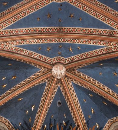 Zdjęcie nr 90: Kościół położony na południe od rynku, na placu otoczonym kamiennym murem z dwiema bramkami od zachodu i północy oraz bramką od południa. Kościół jednonawowy, dwuprzęsłowy, z węższym, niższym dwuprzęsłowym prezbiterium zamkniętym pięciobocznie. Do prezbiterium przylegają dwa aneksy, od północy dawna zakrystia (obecnie kaplica świętych Męczennic), zamknięta od wschodu dwubocznie, mająca w narożu z korpusem wieżyczkę schodową, a od południa zakrystia nowa, na planie prostokąta. Do nawy przylegają dwie kaplice: od północy kaplica Lubomirskich, założona na rzucie kwadratu, nakryta kopułą, a od południa kaplica Branickich, także na rzucie kwadratu z kopułą. Przy korpusie od zachodu piętrowa kruchta, pierwotnie otwarta w przyziemiu od północy, zachodu i południa ostrołukowymi arkadami. Arkada tęczy ostrołukowa. Sklepienie prezbiterium, zakrystii i obu kondygnacjach kruchty krzyżowo-żebrowe, w korpusie, pierwotnie trójprzęsłowym, pierwotnie sklepienie o polach trójkątnych z trójpromieniem, wsparte na dwóch dziesięciobocznych filarach, obecnie kolebkowo z lunetami. Żebra w prezbiterium i zakrystii o profilu żłobkowym, w kruchcie - gruszkowym. W prezbiterium służki cylindryczne, nadwieszone na oplecionych liśćmi wspornikach oraz rzeźbione zworniki z przedstawieniem Głowy Chrystusa i motywami roślinnymi. Ściany rozczłonkowane wykonanymi w czarnego marmuru arkadami, zamkniętymi łukiem półkolistymi. Okna ostrołukowe , obustronnie rozglifione z krzyżowym laskowaniem, w ścianie północnym prezbiterium ślepe. Kościół opięty przyporami. Elewacje na cokole, z profilowanymi gzymsami cokołowymi, kapnikowym i koronującym. Szczyty zwieńczone kwiatonami, z których zachodnie z krzyżem. Portale kamienne, ostrołukowe: zachodni profilowany, z ażurowym maswerkiem; drugi w prezbiterium do zakrystii, profilowany; trzeci do wieżyczki schodowej.