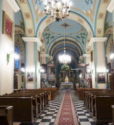 Zdjęcie nr 8: Kościół orientowany, murowany, trójnawowy, halowy, na rzucie prostokąta z wydłużonym, skierowanym na północ prezbiterium z dobudowaną zakrystią i skarbcem. Prezbiterium dwuprzęsłowe, węższe i niższe od korpusu, zamknięte prosto, z arkadową wnęką od strony wnętrza. Na łuku tęczowym napis „SERCE JEZUSA KRÓLOJ NAM”. Nawa główna oraz boczne trójprzęsłowe, rozdzielone masywnymi opilastrowanymi filarami; artykulacja ścian kontynuuje podziały sklepienia, którego szerokie gurty przechodzą w pilastry. Sklepienie prezbiterium oraz naw żagielkowe, przedzielone gurtami. Od południa chór muzyczny mieszczący się między pierwszymi filarami i powyżej kruchty wejściowej. W prezbiterium cztery okna w kształcie stojącego prostokąta zamknięte łukiem półkolistym oraz po dwa mniejsze, ale powtarzające ich kształt w skarbcu i zakrystii. W nawach bocznych po trzy okna wyznaczające środek każdego przęsła, naprzemiennie o opisanym kształcie oraz okulusy; w fasadzie powyżej wejścia okulus, wieża przepruta z każdej strony prostokątnym oknem zamkniętym półkoliście. Główne wejście od wschodu, po jednym od północy, południa, do zakrystii, do skarbca oraz między wymienionymi pomieszczeniami a prezbiterium. Ściany i sklepienia kościoła pokrywa polichromia skomponowana z dekoracji floralnych i floralno-geometrycznych oraz umieszczonych w jej obrębie symboli m.in. ewangelistów. Fasada wieżowa, trójosiowa, jednoprzęsłowa, z widocznym wątkiem kamiennym w dolnej i otynkowana w górnej części. Środkowa oś wyższa; podziały pionowe przeprowadzono za pomocą pilastrów, kondygnacje zamknięto gzymsem poziomym w osiach bocznych oraz wyniesionym i wyłamanym w środkowej. W osi środkowej portal w kształcie stojącego prostokąta zamkniętego łukiem półkolistym w szerokim rozglifieniu, a powyżej okulus. Zamykający kondygnacje trójkątny przyczółek dekorowany od dołu fryzem arkadkowym ułożonym schodkowo, ujmującym półokrągłą, konchową wnękę z figurą Matki Boskiej z Lourdes. W osiach bocznych większe wnęki powtarzające kształt opisanej, wypełnione figurami św. Cyryla i Metodego. Powyżej widoczna wieża, której kondygnacja jest przepruta oknami i zwieńczona gzymsem wyłamanym na osiach; w trójkątnych polach ślepe okulusy. Elewacje boczne z ciosu kamiennego przeprute jedynie oknami i portalami, zamknięte gzymsem o fryzie  wypełnionym prostokątnymi wnękami i gzymsie z ząbkowaniem. Nawy oraz prezbiterium przykrywają dachy dwuspadowe, zakrystię oraz skarbiec pulpitowe, wieżę namiotowy z fartuchem zwieńczony kulą z krzyżem. 
Do najciekawszych elementów wyposażenia należy neośredniowieczny ołtarz główny oraz rokokowa ambona z antyamboną. Najstarszym zabytkiem w posiadaniu kościoła św. Wojciecha jest tzw. „czarna Madonna” – umieszczona w późniejszym feretronie niewielka figurka Matki Boskiej z Dzieciątkiem pochodząca z XIV wieku. 
