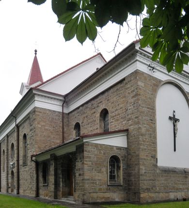 Zdjęcie nr 4: Kościół orientowany, murowany, trójnawowy, halowy, na rzucie prostokąta z wydłużonym, skierowanym na północ prezbiterium z dobudowaną zakrystią i skarbcem. Prezbiterium dwuprzęsłowe, węższe i niższe od korpusu, zamknięte prosto, z arkadową wnęką od strony wnętrza. Na łuku tęczowym napis „SERCE JEZUSA KRÓLOJ NAM”. Nawa główna oraz boczne trójprzęsłowe, rozdzielone masywnymi opilastrowanymi filarami; artykulacja ścian kontynuuje podziały sklepienia, którego szerokie gurty przechodzą w pilastry. Sklepienie prezbiterium oraz naw żagielkowe, przedzielone gurtami. Od południa chór muzyczny mieszczący się między pierwszymi filarami i powyżej kruchty wejściowej. W prezbiterium cztery okna w kształcie stojącego prostokąta zamknięte łukiem półkolistym oraz po dwa mniejsze, ale powtarzające ich kształt w skarbcu i zakrystii. W nawach bocznych po trzy okna wyznaczające środek każdego przęsła, naprzemiennie o opisanym kształcie oraz okulusy; w fasadzie powyżej wejścia okulus, wieża przepruta z każdej strony prostokątnym oknem zamkniętym półkoliście. Główne wejście od wschodu, po jednym od północy, południa, do zakrystii, do skarbca oraz między wymienionymi pomieszczeniami a prezbiterium. Ściany i sklepienia kościoła pokrywa polichromia skomponowana z dekoracji floralnych i floralno-geometrycznych oraz umieszczonych w jej obrębie symboli m.in. ewangelistów. Fasada wieżowa, trójosiowa, jednoprzęsłowa, z widocznym wątkiem kamiennym w dolnej i otynkowana w górnej części. Środkowa oś wyższa; podziały pionowe przeprowadzono za pomocą pilastrów, kondygnacje zamknięto gzymsem poziomym w osiach bocznych oraz wyniesionym i wyłamanym w środkowej. W osi środkowej portal w kształcie stojącego prostokąta zamkniętego łukiem półkolistym w szerokim rozglifieniu, a powyżej okulus. Zamykający kondygnacje trójkątny przyczółek dekorowany od dołu fryzem arkadkowym ułożonym schodkowo, ujmującym półokrągłą, konchową wnękę z figurą Matki Boskiej z Lourdes. W osiach bocznych większe wnęki powtarzające kształt opisanej, wypełnione figurami św. Cyryla i Metodego. Powyżej widoczna wieża, której kondygnacja jest przepruta oknami i zwieńczona gzymsem wyłamanym na osiach; w trójkątnych polach ślepe okulusy. Elewacje boczne z ciosu kamiennego przeprute jedynie oknami i portalami, zamknięte gzymsem o fryzie  wypełnionym prostokątnymi wnękami i gzymsie z ząbkowaniem. Nawy oraz prezbiterium przykrywają dachy dwuspadowe, zakrystię oraz skarbiec pulpitowe, wieżę namiotowy z fartuchem zwieńczony kulą z krzyżem. 
Do najciekawszych elementów wyposażenia należy neośredniowieczny ołtarz główny oraz rokokowa ambona z antyamboną. Najstarszym zabytkiem w posiadaniu kościoła św. Wojciecha jest tzw. „czarna Madonna” – umieszczona w późniejszym feretronie niewielka figurka Matki Boskiej z Dzieciątkiem pochodząca z XIV wieku. 
