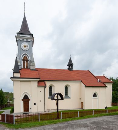 Zdjęcie nr 8: Kościół murowany, tynkowany, jednonawowy. Prezbiterium prostokątne, zamknięte prosto, z obu stron przy nawie prostokątne, piętrowe lokalności (zakrystia i skarbiec, empory). Nawa szersza od prezbiterium, na rzucie prostokąta, od frontu przylega wieża na planie kwadratu z dwoma aneksami po bokach. Prezbiterium dwuprzęsłowe, podzielone wewnątrz pilastrami, sklepione żagielkowo na gurtach. Empory flankowane parami półkolumienek, z oknami w formie leżącego prostokąta zamkniętego łukiem odcinkowym, nad lewą herb Odrowąż z inicjałami „JG”. Nawa nakryta pozornym, spłaszczonym sklepieniem kolebkowym. Otwór tęczowy w formie półkolistej arkady wspartej na pilastrach, z belką o fantazyjnym kształcie. Chór muzyczny dwukondygnacyjny, wsparty na dwóch filarach i dwóch półfilarach, pomiędzy którymi arkady ostrołukowe, kondygnacja zamknięta profilowanym gzymsem. Druga kondygnacja z trzema arkadami, w środkowej organ z wklęsło-wypukłą, ażurową balustradą. Posadzka z płyt ceramicznych. 
Fasada trójosiowa, dwukondygnacyjna. Pierwsza kondygnacja wydzielona pilastrami dekorowanymi blendami, zwieńczona profilowanym gzymsem z fryzem arkadkowym. Nad pilastrami osi bocznych dwie stylizowane wieżyczki, zakończone krzyżami. 
Na każdej osi ostrołukowe arkady, w środkowej wejście, dwie boczne wypełnione stylizowanymi blendami; nad nimi otwory okienne. Na osi środkowej, w drugiej kondygnacji wieża, ujęta w narożach czterema wieżyczkami, ścianki flankowane lizenami, zakończona profilowanym gzymsem z kostkowaniem. Na ściankach z czterech stron tarcze zegarowe oraz otwory dzwonne w formie ostrołukowych arkad w opaskach tynkowych. Wieża nakryta dachem ostrosłupowym. 
Elewacje gładkie, tynkowane zakończone profilowanym gzymsem. Wyodrębnione aneksy elewacji bocznych ujęte grubymi lizenami, z ostrołukowymi arkadami w polu, ujętymi opaskami tynkowymi. Od strony fasady w partiach aneksów bocznych wejścia do kościoła, od strony prezbiterium ostrołukowe okienka. Na każdej elewacji bocznej po trzy okna w formie stojącego prostokąta zamkniętego łukiem półkolistym, o szerokich rozglifieniach, po dwa w nawie i jednym w prezbiterium. Elewacja zamykająca prezbiterium trójosiowa, wydzielona lizenami, z głębokimi wnękami w formie stojącego prostokąta zamkniętego łukiem półkolistym, z namalowanym wizerunkiem Ukrzyżowanego Chrystusa i dwóch łotrów na krzyżach. Elewacja zakończona profilowanym gzymsem, z daszkiem pulpitowym oraz trójkątnym szczytem z czterema cokołami. Nawa i prezbiterium nakryte osobnymi  dachami dwuspadowymi. Na połączeniu nawy i aneksów przy prezbiterium wieżyczka na sygnaturkę z latarnią, nakryta dachem ostrosłupowym. 


