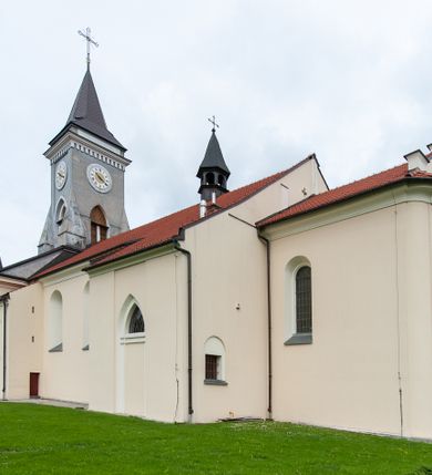 Zdjęcie nr 12: Kościół murowany, tynkowany, jednonawowy. Prezbiterium prostokątne, zamknięte prosto, z obu stron przy nawie prostokątne, piętrowe lokalności (zakrystia i skarbiec, empory). Nawa szersza od prezbiterium, na rzucie prostokąta, od frontu przylega wieża na planie kwadratu z dwoma aneksami po bokach. Prezbiterium dwuprzęsłowe, podzielone wewnątrz pilastrami, sklepione żagielkowo na gurtach. Empory flankowane parami półkolumienek, z oknami w formie leżącego prostokąta zamkniętego łukiem odcinkowym, nad lewą herb Odrowąż z inicjałami „JG”. Nawa nakryta pozornym, spłaszczonym sklepieniem kolebkowym. Otwór tęczowy w formie półkolistej arkady wspartej na pilastrach, z belką o fantazyjnym kształcie. Chór muzyczny dwukondygnacyjny, wsparty na dwóch filarach i dwóch półfilarach, pomiędzy którymi arkady ostrołukowe, kondygnacja zamknięta profilowanym gzymsem. Druga kondygnacja z trzema arkadami, w środkowej organ z wklęsło-wypukłą, ażurową balustradą. Posadzka z płyt ceramicznych. 
Fasada trójosiowa, dwukondygnacyjna. Pierwsza kondygnacja wydzielona pilastrami dekorowanymi blendami, zwieńczona profilowanym gzymsem z fryzem arkadkowym. Nad pilastrami osi bocznych dwie stylizowane wieżyczki, zakończone krzyżami. 
Na każdej osi ostrołukowe arkady, w środkowej wejście, dwie boczne wypełnione stylizowanymi blendami; nad nimi otwory okienne. Na osi środkowej, w drugiej kondygnacji wieża, ujęta w narożach czterema wieżyczkami, ścianki flankowane lizenami, zakończona profilowanym gzymsem z kostkowaniem. Na ściankach z czterech stron tarcze zegarowe oraz otwory dzwonne w formie ostrołukowych arkad w opaskach tynkowych. Wieża nakryta dachem ostrosłupowym. 
Elewacje gładkie, tynkowane zakończone profilowanym gzymsem. Wyodrębnione aneksy elewacji bocznych ujęte grubymi lizenami, z ostrołukowymi arkadami w polu, ujętymi opaskami tynkowymi. Od strony fasady w partiach aneksów bocznych wejścia do kościoła, od strony prezbiterium ostrołukowe okienka. Na każdej elewacji bocznej po trzy okna w formie stojącego prostokąta zamkniętego łukiem półkolistym, o szerokich rozglifieniach, po dwa w nawie i jednym w prezbiterium. Elewacja zamykająca prezbiterium trójosiowa, wydzielona lizenami, z głębokimi wnękami w formie stojącego prostokąta zamkniętego łukiem półkolistym, z namalowanym wizerunkiem Ukrzyżowanego Chrystusa i dwóch łotrów na krzyżach. Elewacja zakończona profilowanym gzymsem, z daszkiem pulpitowym oraz trójkątnym szczytem z czterema cokołami. Nawa i prezbiterium nakryte osobnymi  dachami dwuspadowymi. Na połączeniu nawy i aneksów przy prezbiterium wieżyczka na sygnaturkę z latarnią, nakryta dachem ostrosłupowym. 



