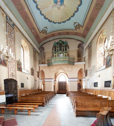 Zdjęcie nr 30: Kościół murowany, tynkowany, jednonawowy. Prezbiterium prostokątne, zamknięte prosto, z obu stron przy nawie prostokątne, piętrowe lokalności (zakrystia i skarbiec, empory). Nawa szersza od prezbiterium, na rzucie prostokąta, od frontu przylega wieża na planie kwadratu z dwoma aneksami po bokach. Prezbiterium dwuprzęsłowe, podzielone wewnątrz pilastrami, sklepione żagielkowo na gurtach. Empory flankowane parami półkolumienek, z oknami w formie leżącego prostokąta zamkniętego łukiem odcinkowym, nad lewą herb Odrowąż z inicjałami „JG”. Nawa nakryta pozornym, spłaszczonym sklepieniem kolebkowym. Otwór tęczowy w formie półkolistej arkady wspartej na pilastrach, z belką o fantazyjnym kształcie. Chór muzyczny dwukondygnacyjny, wsparty na dwóch filarach i dwóch półfilarach, pomiędzy którymi arkady ostrołukowe, kondygnacja zamknięta profilowanym gzymsem. Druga kondygnacja z trzema arkadami, w środkowej organ z wklęsło-wypukłą, ażurową balustradą. Posadzka z płyt ceramicznych. 
Fasada trójosiowa, dwukondygnacyjna. Pierwsza kondygnacja wydzielona pilastrami dekorowanymi blendami, zwieńczona profilowanym gzymsem z fryzem arkadkowym. Nad pilastrami osi bocznych dwie stylizowane wieżyczki, zakończone krzyżami. 
Na każdej osi ostrołukowe arkady, w środkowej wejście, dwie boczne wypełnione stylizowanymi blendami; nad nimi otwory okienne. Na osi środkowej, w drugiej kondygnacji wieża, ujęta w narożach czterema wieżyczkami, ścianki flankowane lizenami, zakończona profilowanym gzymsem z kostkowaniem. Na ściankach z czterech stron tarcze zegarowe oraz otwory dzwonne w formie ostrołukowych arkad w opaskach tynkowych. Wieża nakryta dachem ostrosłupowym. 
Elewacje gładkie, tynkowane zakończone profilowanym gzymsem. Wyodrębnione aneksy elewacji bocznych ujęte grubymi lizenami, z ostrołukowymi arkadami w polu, ujętymi opaskami tynkowymi. Od strony fasady w partiach aneksów bocznych wejścia do kościoła, od strony prezbiterium ostrołukowe okienka. Na każdej elewacji bocznej po trzy okna w formie stojącego prostokąta zamkniętego łukiem półkolistym, o szerokich rozglifieniach, po dwa w nawie i jednym w prezbiterium. Elewacja zamykająca prezbiterium trójosiowa, wydzielona lizenami, z głębokimi wnękami w formie stojącego prostokąta zamkniętego łukiem półkolistym, z namalowanym wizerunkiem Ukrzyżowanego Chrystusa i dwóch łotrów na krzyżach. Elewacja zakończona profilowanym gzymsem, z daszkiem pulpitowym oraz trójkątnym szczytem z czterema cokołami. Nawa i prezbiterium nakryte osobnymi  dachami dwuspadowymi. Na połączeniu nawy i aneksów przy prezbiterium wieżyczka na sygnaturkę z latarnią, nakryta dachem ostrosłupowym. 


