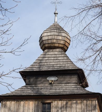 Zdjęcie nr 4: Kościół Nawiedzenia Najświętszej Marii Panny jest usytuowany w centrum wsi, na południe od głównej drogi wiodącej przez Paczółtowice. Teren przykościelny z umiejscowionym w północnej części cmentarzem otacza niewysoki, kamienny i częściowo ceglany mur nakryty dwuspadowym daszkiem. Prowadzą do niego dwa wejścia – usytuowana w północno-zachodnim narożniku muru brama z figurami Matki Boskiej i Chrystusa oraz nieco skromniejsze wejście od strony południowej. W północno-wschodniej części placu przykościelnego znajduje się wolnostojąca dzwonnica założona na planie czworoboku. Natomiast w części południowo-wschodniej umiejscowiona jest kamienna grota mieszcząca figurę Matki Boskiej z Lourdes. Kościół paczółtowicki to niewielkich rozmiarów, orientowana i jednonawowa budowla o konstrukcji drewnianej; kryta gontem. Fundamenty świątyni są murowane i tynkowane, odsadzkę pomiędzy fundamentem i zrębem przykrywa niewielki okap z gontu. Ściany zewnętrzne kościoła oszalowano pionowymi deskami z nabitymi dla wzmocnienia listwami. Zamknięte wielobocznie prezbiterium, przekryte dachem trójpołaciowym przylega do nieco szerszej nawy założonej na rzucie zbliżonym do kwadratu. Nawa nakryta jest dachem dwuspadowym. Prowadzą do niej dwa wejścia: główne, od zachodu, spod wieży i od strony południowej. Okna wychodzą wyłącznie na południe i umieszczone są parami w nawie, z zachowanymi oryginalnymi obramieniami i w prezbiterium, gdzie były zmienione w czasie późniejszym. Przy prezbiterium od strony północnej znajduje się zakrystia na rzucie prostokąta nakryta jednospadowym dachem; dostępna od strony wschodniej. Do nawy od strony południowej przylega niewielka kruchta również na rzucie prostokąta, nakryta dwuspadowym dachem. W elewacji zachodniej znajduje się kwadratowa wieża dzwonna o ścianach lekko pochyłych, w połowie wysokości podzielonych gzymsem. Nakryta jest hełmem o kształcie daszka namiotowego zamkniętego od góry cebulastą kopułką zwieńczoną krzyżem. W zachodniej ścianie wieży znajduje się wejście główne do kościoła przykryte daszkiem dwuspadowym. Na ścianie południowej dwa okna zwieńczone trójkątnymi daszkami. Od strony północnej, zachodniej i południowej po jednym oknie umiejscowionym pod dachem wieży. Ośmioboczna wieżyczka na sygnaturkę nakryta jest rozbudowanym, barokowym hełmem z pseudoglorietą również zwieńczonym krzyżem. Nawa i prezbiterium przekryte  są wspólnym stropem (w nawie z zaskrzynieniami; belki zaskrzynień profilowane). Między nawą a prezbiterium mieści się ściana tęczowa z otworem tęczowym w formie ostrołukowej arkady. Na wysokości trzech czwartych wysokości nawy umieszczona jest poprzeczna belka tęczowa. W zachodniej części nawy znajduje się drewniany chór muzyczny wsparty na profilowanych, drewnianych kolumnach. Odrzwia w nawie od zachodu i południa z nadprożami wyciętymi w ośli grzbiet; okna w nawie z nadokiennikami o takim samym wykroju. Drzwi prowadzące z prezbiterium do zakrystii żelazne z listwami w skośną kratę, z antabą i zamkiem. Posadzka w nawie i prezbiterium marmurowa.
