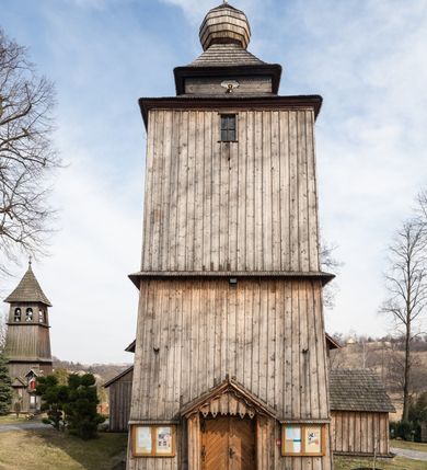 Zdjęcie nr 3: Kościół Nawiedzenia Najświętszej Marii Panny jest usytuowany w centrum wsi, na południe od głównej drogi wiodącej przez Paczółtowice. Teren przykościelny z umiejscowionym w północnej części cmentarzem otacza niewysoki, kamienny i częściowo ceglany mur nakryty dwuspadowym daszkiem. Prowadzą do niego dwa wejścia – usytuowana w północno-zachodnim narożniku muru brama z figurami Matki Boskiej i Chrystusa oraz nieco skromniejsze wejście od strony południowej. W północno-wschodniej części placu przykościelnego znajduje się wolnostojąca dzwonnica założona na planie czworoboku. Natomiast w części południowo-wschodniej umiejscowiona jest kamienna grota mieszcząca figurę Matki Boskiej z Lourdes. Kościół paczółtowicki to niewielkich rozmiarów, orientowana i jednonawowa budowla o konstrukcji drewnianej; kryta gontem. Fundamenty świątyni są murowane i tynkowane, odsadzkę pomiędzy fundamentem i zrębem przykrywa niewielki okap z gontu. Ściany zewnętrzne kościoła oszalowano pionowymi deskami z nabitymi dla wzmocnienia listwami. Zamknięte wielobocznie prezbiterium, przekryte dachem trójpołaciowym przylega do nieco szerszej nawy założonej na rzucie zbliżonym do kwadratu. Nawa nakryta jest dachem dwuspadowym. Prowadzą do niej dwa wejścia: główne, od zachodu, spod wieży i od strony południowej. Okna wychodzą wyłącznie na południe i umieszczone są parami w nawie, z zachowanymi oryginalnymi obramieniami i w prezbiterium, gdzie były zmienione w czasie późniejszym. Przy prezbiterium od strony północnej znajduje się zakrystia na rzucie prostokąta nakryta jednospadowym dachem; dostępna od strony wschodniej. Do nawy od strony południowej przylega niewielka kruchta również na rzucie prostokąta, nakryta dwuspadowym dachem. W elewacji zachodniej znajduje się kwadratowa wieża dzwonna o ścianach lekko pochyłych, w połowie wysokości podzielonych gzymsem. Nakryta jest hełmem o kształcie daszka namiotowego zamkniętego od góry cebulastą kopułką zwieńczoną krzyżem. W zachodniej ścianie wieży znajduje się wejście główne do kościoła przykryte daszkiem dwuspadowym. Na ścianie południowej dwa okna zwieńczone trójkątnymi daszkami. Od strony północnej, zachodniej i południowej po jednym oknie umiejscowionym pod dachem wieży. Ośmioboczna wieżyczka na sygnaturkę nakryta jest rozbudowanym, barokowym hełmem z pseudoglorietą również zwieńczonym krzyżem. Nawa i prezbiterium przekryte  są wspólnym stropem (w nawie z zaskrzynieniami; belki zaskrzynień profilowane). Między nawą a prezbiterium mieści się ściana tęczowa z otworem tęczowym w formie ostrołukowej arkady. Na wysokości trzech czwartych wysokości nawy umieszczona jest poprzeczna belka tęczowa. W zachodniej części nawy znajduje się drewniany chór muzyczny wsparty na profilowanych, drewnianych kolumnach. Odrzwia w nawie od zachodu i południa z nadprożami wyciętymi w ośli grzbiet; okna w nawie z nadokiennikami o takim samym wykroju. Drzwi prowadzące z prezbiterium do zakrystii żelazne z listwami w skośną kratę, z antabą i zamkiem. Posadzka w nawie i prezbiterium marmurowa.
