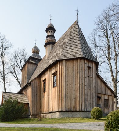 Zdjęcie nr 15: Kościół Nawiedzenia Najświętszej Marii Panny jest usytuowany w centrum wsi, na południe od głównej drogi wiodącej przez Paczółtowice. Teren przykościelny z umiejscowionym w północnej części cmentarzem otacza niewysoki, kamienny i częściowo ceglany mur nakryty dwuspadowym daszkiem. Prowadzą do niego dwa wejścia – usytuowana w północno-zachodnim narożniku muru brama z figurami Matki Boskiej i Chrystusa oraz nieco skromniejsze wejście od strony południowej. W północno-wschodniej części placu przykościelnego znajduje się wolnostojąca dzwonnica założona na planie czworoboku. Natomiast w części południowo-wschodniej umiejscowiona jest kamienna grota mieszcząca figurę Matki Boskiej z Lourdes. Kościół paczółtowicki to niewielkich rozmiarów, orientowana i jednonawowa budowla o konstrukcji drewnianej; kryta gontem. Fundamenty świątyni są murowane i tynkowane, odsadzkę pomiędzy fundamentem i zrębem przykrywa niewielki okap z gontu. Ściany zewnętrzne kościoła oszalowano pionowymi deskami z nabitymi dla wzmocnienia listwami. Zamknięte wielobocznie prezbiterium, przekryte dachem trójpołaciowym przylega do nieco szerszej nawy założonej na rzucie zbliżonym do kwadratu. Nawa nakryta jest dachem dwuspadowym. Prowadzą do niej dwa wejścia: główne, od zachodu, spod wieży i od strony południowej. Okna wychodzą wyłącznie na południe i umieszczone są parami w nawie, z zachowanymi oryginalnymi obramieniami i w prezbiterium, gdzie były zmienione w czasie późniejszym. Przy prezbiterium od strony północnej znajduje się zakrystia na rzucie prostokąta nakryta jednospadowym dachem; dostępna od strony wschodniej. Do nawy od strony południowej przylega niewielka kruchta również na rzucie prostokąta, nakryta dwuspadowym dachem. W elewacji zachodniej znajduje się kwadratowa wieża dzwonna o ścianach lekko pochyłych, w połowie wysokości podzielonych gzymsem. Nakryta jest hełmem o kształcie daszka namiotowego zamkniętego od góry cebulastą kopułką zwieńczoną krzyżem. W zachodniej ścianie wieży znajduje się wejście główne do kościoła przykryte daszkiem dwuspadowym. Na ścianie południowej dwa okna zwieńczone trójkątnymi daszkami. Od strony północnej, zachodniej i południowej po jednym oknie umiejscowionym pod dachem wieży. Ośmioboczna wieżyczka na sygnaturkę nakryta jest rozbudowanym, barokowym hełmem z pseudoglorietą również zwieńczonym krzyżem. Nawa i prezbiterium przekryte  są wspólnym stropem (w nawie z zaskrzynieniami; belki zaskrzynień profilowane). Między nawą a prezbiterium mieści się ściana tęczowa z otworem tęczowym w formie ostrołukowej arkady. Na wysokości trzech czwartych wysokości nawy umieszczona jest poprzeczna belka tęczowa. W zachodniej części nawy znajduje się drewniany chór muzyczny wsparty na profilowanych, drewnianych kolumnach. Odrzwia w nawie od zachodu i południa z nadprożami wyciętymi w ośli grzbiet; okna w nawie z nadokiennikami o takim samym wykroju. Drzwi prowadzące z prezbiterium do zakrystii żelazne z listwami w skośną kratę, z antabą i zamkiem. Posadzka w nawie i prezbiterium marmurowa.
