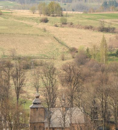 Zdjęcie nr 11: Kościół Nawiedzenia Najświętszej Marii Panny jest usytuowany w centrum wsi, na południe od głównej drogi wiodącej przez Paczółtowice. Teren przykościelny z umiejscowionym w północnej części cmentarzem otacza niewysoki, kamienny i częściowo ceglany mur nakryty dwuspadowym daszkiem. Prowadzą do niego dwa wejścia – usytuowana w północno-zachodnim narożniku muru brama z figurami Matki Boskiej i Chrystusa oraz nieco skromniejsze wejście od strony południowej. W północno-wschodniej części placu przykościelnego znajduje się wolnostojąca dzwonnica założona na planie czworoboku. Natomiast w części południowo-wschodniej umiejscowiona jest kamienna grota mieszcząca figurę Matki Boskiej z Lourdes. Kościół paczółtowicki to niewielkich rozmiarów, orientowana i jednonawowa budowla o konstrukcji drewnianej; kryta gontem. Fundamenty świątyni są murowane i tynkowane, odsadzkę pomiędzy fundamentem i zrębem przykrywa niewielki okap z gontu. Ściany zewnętrzne kościoła oszalowano pionowymi deskami z nabitymi dla wzmocnienia listwami. Zamknięte wielobocznie prezbiterium, przekryte dachem trójpołaciowym przylega do nieco szerszej nawy założonej na rzucie zbliżonym do kwadratu. Nawa nakryta jest dachem dwuspadowym. Prowadzą do niej dwa wejścia: główne, od zachodu, spod wieży i od strony południowej. Okna wychodzą wyłącznie na południe i umieszczone są parami w nawie, z zachowanymi oryginalnymi obramieniami i w prezbiterium, gdzie były zmienione w czasie późniejszym. Przy prezbiterium od strony północnej znajduje się zakrystia na rzucie prostokąta nakryta jednospadowym dachem; dostępna od strony wschodniej. Do nawy od strony południowej przylega niewielka kruchta również na rzucie prostokąta, nakryta dwuspadowym dachem. W elewacji zachodniej znajduje się kwadratowa wieża dzwonna o ścianach lekko pochyłych, w połowie wysokości podzielonych gzymsem. Nakryta jest hełmem o kształcie daszka namiotowego zamkniętego od góry cebulastą kopułką zwieńczoną krzyżem. W zachodniej ścianie wieży znajduje się wejście główne do kościoła przykryte daszkiem dwuspadowym. Na ścianie południowej dwa okna zwieńczone trójkątnymi daszkami. Od strony północnej, zachodniej i południowej po jednym oknie umiejscowionym pod dachem wieży. Ośmioboczna wieżyczka na sygnaturkę nakryta jest rozbudowanym, barokowym hełmem z pseudoglorietą również zwieńczonym krzyżem. Nawa i prezbiterium przekryte  są wspólnym stropem (w nawie z zaskrzynieniami; belki zaskrzynień profilowane). Między nawą a prezbiterium mieści się ściana tęczowa z otworem tęczowym w formie ostrołukowej arkady. Na wysokości trzech czwartych wysokości nawy umieszczona jest poprzeczna belka tęczowa. W zachodniej części nawy znajduje się drewniany chór muzyczny wsparty na profilowanych, drewnianych kolumnach. Odrzwia w nawie od zachodu i południa z nadprożami wyciętymi w ośli grzbiet; okna w nawie z nadokiennikami o takim samym wykroju. Drzwi prowadzące z prezbiterium do zakrystii żelazne z listwami w skośną kratę, z antabą i zamkiem. Posadzka w nawie i prezbiterium marmurowa.
