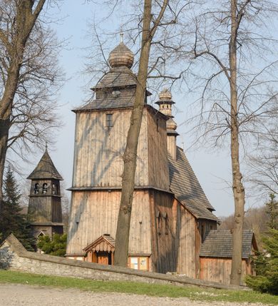 Zdjęcie nr 26: Kościół Nawiedzenia Najświętszej Marii Panny jest usytuowany w centrum wsi, na południe od głównej drogi wiodącej przez Paczółtowice. Teren przykościelny z umiejscowionym w północnej części cmentarzem otacza niewysoki, kamienny i częściowo ceglany mur nakryty dwuspadowym daszkiem. Prowadzą do niego dwa wejścia – usytuowana w północno-zachodnim narożniku muru brama z figurami Matki Boskiej i Chrystusa oraz nieco skromniejsze wejście od strony południowej. W północno-wschodniej części placu przykościelnego znajduje się wolnostojąca dzwonnica założona na planie czworoboku. Natomiast w części południowo-wschodniej umiejscowiona jest kamienna grota mieszcząca figurę Matki Boskiej z Lourdes. Kościół paczółtowicki to niewielkich rozmiarów, orientowana i jednonawowa budowla o konstrukcji drewnianej; kryta gontem. Fundamenty świątyni są murowane i tynkowane, odsadzkę pomiędzy fundamentem i zrębem przykrywa niewielki okap z gontu. Ściany zewnętrzne kościoła oszalowano pionowymi deskami z nabitymi dla wzmocnienia listwami. Zamknięte wielobocznie prezbiterium, przekryte dachem trójpołaciowym przylega do nieco szerszej nawy założonej na rzucie zbliżonym do kwadratu. Nawa nakryta jest dachem dwuspadowym. Prowadzą do niej dwa wejścia: główne, od zachodu, spod wieży i od strony południowej. Okna wychodzą wyłącznie na południe i umieszczone są parami w nawie, z zachowanymi oryginalnymi obramieniami i w prezbiterium, gdzie były zmienione w czasie późniejszym. Przy prezbiterium od strony północnej znajduje się zakrystia na rzucie prostokąta nakryta jednospadowym dachem; dostępna od strony wschodniej. Do nawy od strony południowej przylega niewielka kruchta również na rzucie prostokąta, nakryta dwuspadowym dachem. W elewacji zachodniej znajduje się kwadratowa wieża dzwonna o ścianach lekko pochyłych, w połowie wysokości podzielonych gzymsem. Nakryta jest hełmem o kształcie daszka namiotowego zamkniętego od góry cebulastą kopułką zwieńczoną krzyżem. W zachodniej ścianie wieży znajduje się wejście główne do kościoła przykryte daszkiem dwuspadowym. Na ścianie południowej dwa okna zwieńczone trójkątnymi daszkami. Od strony północnej, zachodniej i południowej po jednym oknie umiejscowionym pod dachem wieży. Ośmioboczna wieżyczka na sygnaturkę nakryta jest rozbudowanym, barokowym hełmem z pseudoglorietą również zwieńczonym krzyżem. Nawa i prezbiterium przekryte  są wspólnym stropem (w nawie z zaskrzynieniami; belki zaskrzynień profilowane). Między nawą a prezbiterium mieści się ściana tęczowa z otworem tęczowym w formie ostrołukowej arkady. Na wysokości trzech czwartych wysokości nawy umieszczona jest poprzeczna belka tęczowa. W zachodniej części nawy znajduje się drewniany chór muzyczny wsparty na profilowanych, drewnianych kolumnach. Odrzwia w nawie od zachodu i południa z nadprożami wyciętymi w ośli grzbiet; okna w nawie z nadokiennikami o takim samym wykroju. Drzwi prowadzące z prezbiterium do zakrystii żelazne z listwami w skośną kratę, z antabą i zamkiem. Posadzka w nawie i prezbiterium marmurowa.
