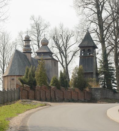 Zdjęcie nr 8: Kościół Nawiedzenia Najświętszej Marii Panny jest usytuowany w centrum wsi, na południe od głównej drogi wiodącej przez Paczółtowice. Teren przykościelny z umiejscowionym w północnej części cmentarzem otacza niewysoki, kamienny i częściowo ceglany mur nakryty dwuspadowym daszkiem. Prowadzą do niego dwa wejścia – usytuowana w północno-zachodnim narożniku muru brama z figurami Matki Boskiej i Chrystusa oraz nieco skromniejsze wejście od strony południowej. W północno-wschodniej części placu przykościelnego znajduje się wolnostojąca dzwonnica założona na planie czworoboku. Natomiast w części południowo-wschodniej umiejscowiona jest kamienna grota mieszcząca figurę Matki Boskiej z Lourdes. Kościół paczółtowicki to niewielkich rozmiarów, orientowana i jednonawowa budowla o konstrukcji drewnianej; kryta gontem. Fundamenty świątyni są murowane i tynkowane, odsadzkę pomiędzy fundamentem i zrębem przykrywa niewielki okap z gontu. Ściany zewnętrzne kościoła oszalowano pionowymi deskami z nabitymi dla wzmocnienia listwami. Zamknięte wielobocznie prezbiterium, przekryte dachem trójpołaciowym przylega do nieco szerszej nawy założonej na rzucie zbliżonym do kwadratu. Nawa nakryta jest dachem dwuspadowym. Prowadzą do niej dwa wejścia: główne, od zachodu, spod wieży i od strony południowej. Okna wychodzą wyłącznie na południe i umieszczone są parami w nawie, z zachowanymi oryginalnymi obramieniami i w prezbiterium, gdzie były zmienione w czasie późniejszym. Przy prezbiterium od strony północnej znajduje się zakrystia na rzucie prostokąta nakryta jednospadowym dachem; dostępna od strony wschodniej. Do nawy od strony południowej przylega niewielka kruchta również na rzucie prostokąta, nakryta dwuspadowym dachem. W elewacji zachodniej znajduje się kwadratowa wieża dzwonna o ścianach lekko pochyłych, w połowie wysokości podzielonych gzymsem. Nakryta jest hełmem o kształcie daszka namiotowego zamkniętego od góry cebulastą kopułką zwieńczoną krzyżem. W zachodniej ścianie wieży znajduje się wejście główne do kościoła przykryte daszkiem dwuspadowym. Na ścianie południowej dwa okna zwieńczone trójkątnymi daszkami. Od strony północnej, zachodniej i południowej po jednym oknie umiejscowionym pod dachem wieży. Ośmioboczna wieżyczka na sygnaturkę nakryta jest rozbudowanym, barokowym hełmem z pseudoglorietą również zwieńczonym krzyżem. Nawa i prezbiterium przekryte  są wspólnym stropem (w nawie z zaskrzynieniami; belki zaskrzynień profilowane). Między nawą a prezbiterium mieści się ściana tęczowa z otworem tęczowym w formie ostrołukowej arkady. Na wysokości trzech czwartych wysokości nawy umieszczona jest poprzeczna belka tęczowa. W zachodniej części nawy znajduje się drewniany chór muzyczny wsparty na profilowanych, drewnianych kolumnach. Odrzwia w nawie od zachodu i południa z nadprożami wyciętymi w ośli grzbiet; okna w nawie z nadokiennikami o takim samym wykroju. Drzwi prowadzące z prezbiterium do zakrystii żelazne z listwami w skośną kratę, z antabą i zamkiem. Posadzka w nawie i prezbiterium marmurowa.
