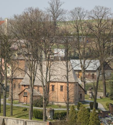 Zdjęcie nr 9: Kościół Nawiedzenia Najświętszej Marii Panny jest usytuowany w centrum wsi, na południe od głównej drogi wiodącej przez Paczółtowice. Teren przykościelny z umiejscowionym w północnej części cmentarzem otacza niewysoki, kamienny i częściowo ceglany mur nakryty dwuspadowym daszkiem. Prowadzą do niego dwa wejścia – usytuowana w północno-zachodnim narożniku muru brama z figurami Matki Boskiej i Chrystusa oraz nieco skromniejsze wejście od strony południowej. W północno-wschodniej części placu przykościelnego znajduje się wolnostojąca dzwonnica założona na planie czworoboku. Natomiast w części południowo-wschodniej umiejscowiona jest kamienna grota mieszcząca figurę Matki Boskiej z Lourdes. Kościół paczółtowicki to niewielkich rozmiarów, orientowana i jednonawowa budowla o konstrukcji drewnianej; kryta gontem. Fundamenty świątyni są murowane i tynkowane, odsadzkę pomiędzy fundamentem i zrębem przykrywa niewielki okap z gontu. Ściany zewnętrzne kościoła oszalowano pionowymi deskami z nabitymi dla wzmocnienia listwami. Zamknięte wielobocznie prezbiterium, przekryte dachem trójpołaciowym przylega do nieco szerszej nawy założonej na rzucie zbliżonym do kwadratu. Nawa nakryta jest dachem dwuspadowym. Prowadzą do niej dwa wejścia: główne, od zachodu, spod wieży i od strony południowej. Okna wychodzą wyłącznie na południe i umieszczone są parami w nawie, z zachowanymi oryginalnymi obramieniami i w prezbiterium, gdzie były zmienione w czasie późniejszym. Przy prezbiterium od strony północnej znajduje się zakrystia na rzucie prostokąta nakryta jednospadowym dachem; dostępna od strony wschodniej. Do nawy od strony południowej przylega niewielka kruchta również na rzucie prostokąta, nakryta dwuspadowym dachem. W elewacji zachodniej znajduje się kwadratowa wieża dzwonna o ścianach lekko pochyłych, w połowie wysokości podzielonych gzymsem. Nakryta jest hełmem o kształcie daszka namiotowego zamkniętego od góry cebulastą kopułką zwieńczoną krzyżem. W zachodniej ścianie wieży znajduje się wejście główne do kościoła przykryte daszkiem dwuspadowym. Na ścianie południowej dwa okna zwieńczone trójkątnymi daszkami. Od strony północnej, zachodniej i południowej po jednym oknie umiejscowionym pod dachem wieży. Ośmioboczna wieżyczka na sygnaturkę nakryta jest rozbudowanym, barokowym hełmem z pseudoglorietą również zwieńczonym krzyżem. Nawa i prezbiterium przekryte  są wspólnym stropem (w nawie z zaskrzynieniami; belki zaskrzynień profilowane). Między nawą a prezbiterium mieści się ściana tęczowa z otworem tęczowym w formie ostrołukowej arkady. Na wysokości trzech czwartych wysokości nawy umieszczona jest poprzeczna belka tęczowa. W zachodniej części nawy znajduje się drewniany chór muzyczny wsparty na profilowanych, drewnianych kolumnach. Odrzwia w nawie od zachodu i południa z nadprożami wyciętymi w ośli grzbiet; okna w nawie z nadokiennikami o takim samym wykroju. Drzwi prowadzące z prezbiterium do zakrystii żelazne z listwami w skośną kratę, z antabą i zamkiem. Posadzka w nawie i prezbiterium marmurowa.
