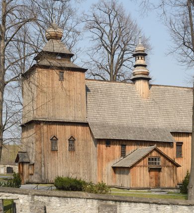 Zdjęcie nr 10: Kościół Nawiedzenia Najświętszej Marii Panny jest usytuowany w centrum wsi, na południe od głównej drogi wiodącej przez Paczółtowice. Teren przykościelny z umiejscowionym w północnej części cmentarzem otacza niewysoki, kamienny i częściowo ceglany mur nakryty dwuspadowym daszkiem. Prowadzą do niego dwa wejścia – usytuowana w północno-zachodnim narożniku muru brama z figurami Matki Boskiej i Chrystusa oraz nieco skromniejsze wejście od strony południowej. W północno-wschodniej części placu przykościelnego znajduje się wolnostojąca dzwonnica założona na planie czworoboku. Natomiast w części południowo-wschodniej umiejscowiona jest kamienna grota mieszcząca figurę Matki Boskiej z Lourdes. Kościół paczółtowicki to niewielkich rozmiarów, orientowana i jednonawowa budowla o konstrukcji drewnianej; kryta gontem. Fundamenty świątyni są murowane i tynkowane, odsadzkę pomiędzy fundamentem i zrębem przykrywa niewielki okap z gontu. Ściany zewnętrzne kościoła oszalowano pionowymi deskami z nabitymi dla wzmocnienia listwami. Zamknięte wielobocznie prezbiterium, przekryte dachem trójpołaciowym przylega do nieco szerszej nawy założonej na rzucie zbliżonym do kwadratu. Nawa nakryta jest dachem dwuspadowym. Prowadzą do niej dwa wejścia: główne, od zachodu, spod wieży i od strony południowej. Okna wychodzą wyłącznie na południe i umieszczone są parami w nawie, z zachowanymi oryginalnymi obramieniami i w prezbiterium, gdzie były zmienione w czasie późniejszym. Przy prezbiterium od strony północnej znajduje się zakrystia na rzucie prostokąta nakryta jednospadowym dachem; dostępna od strony wschodniej. Do nawy od strony południowej przylega niewielka kruchta również na rzucie prostokąta, nakryta dwuspadowym dachem. W elewacji zachodniej znajduje się kwadratowa wieża dzwonna o ścianach lekko pochyłych, w połowie wysokości podzielonych gzymsem. Nakryta jest hełmem o kształcie daszka namiotowego zamkniętego od góry cebulastą kopułką zwieńczoną krzyżem. W zachodniej ścianie wieży znajduje się wejście główne do kościoła przykryte daszkiem dwuspadowym. Na ścianie południowej dwa okna zwieńczone trójkątnymi daszkami. Od strony północnej, zachodniej i południowej po jednym oknie umiejscowionym pod dachem wieży. Ośmioboczna wieżyczka na sygnaturkę nakryta jest rozbudowanym, barokowym hełmem z pseudoglorietą również zwieńczonym krzyżem. Nawa i prezbiterium przekryte  są wspólnym stropem (w nawie z zaskrzynieniami; belki zaskrzynień profilowane). Między nawą a prezbiterium mieści się ściana tęczowa z otworem tęczowym w formie ostrołukowej arkady. Na wysokości trzech czwartych wysokości nawy umieszczona jest poprzeczna belka tęczowa. W zachodniej części nawy znajduje się drewniany chór muzyczny wsparty na profilowanych, drewnianych kolumnach. Odrzwia w nawie od zachodu i południa z nadprożami wyciętymi w ośli grzbiet; okna w nawie z nadokiennikami o takim samym wykroju. Drzwi prowadzące z prezbiterium do zakrystii żelazne z listwami w skośną kratę, z antabą i zamkiem. Posadzka w nawie i prezbiterium marmurowa.
