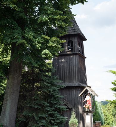 Zdjęcie nr 22: Kościół Nawiedzenia Najświętszej Marii Panny jest usytuowany w centrum wsi, na południe od głównej drogi wiodącej przez Paczółtowice. Teren przykościelny z umiejscowionym w północnej części cmentarzem otacza niewysoki, kamienny i częściowo ceglany mur nakryty dwuspadowym daszkiem. Prowadzą do niego dwa wejścia – usytuowana w północno-zachodnim narożniku muru brama z figurami Matki Boskiej i Chrystusa oraz nieco skromniejsze wejście od strony południowej. W północno-wschodniej części placu przykościelnego znajduje się wolnostojąca dzwonnica założona na planie czworoboku. Natomiast w części południowo-wschodniej umiejscowiona jest kamienna grota mieszcząca figurę Matki Boskiej z Lourdes. Kościół paczółtowicki to niewielkich rozmiarów, orientowana i jednonawowa budowla o konstrukcji drewnianej; kryta gontem. Fundamenty świątyni są murowane i tynkowane, odsadzkę pomiędzy fundamentem i zrębem przykrywa niewielki okap z gontu. Ściany zewnętrzne kościoła oszalowano pionowymi deskami z nabitymi dla wzmocnienia listwami. Zamknięte wielobocznie prezbiterium, przekryte dachem trójpołaciowym przylega do nieco szerszej nawy założonej na rzucie zbliżonym do kwadratu. Nawa nakryta jest dachem dwuspadowym. Prowadzą do niej dwa wejścia: główne, od zachodu, spod wieży i od strony południowej. Okna wychodzą wyłącznie na południe i umieszczone są parami w nawie, z zachowanymi oryginalnymi obramieniami i w prezbiterium, gdzie były zmienione w czasie późniejszym. Przy prezbiterium od strony północnej znajduje się zakrystia na rzucie prostokąta nakryta jednospadowym dachem; dostępna od strony wschodniej. Do nawy od strony południowej przylega niewielka kruchta również na rzucie prostokąta, nakryta dwuspadowym dachem. W elewacji zachodniej znajduje się kwadratowa wieża dzwonna o ścianach lekko pochyłych, w połowie wysokości podzielonych gzymsem. Nakryta jest hełmem o kształcie daszka namiotowego zamkniętego od góry cebulastą kopułką zwieńczoną krzyżem. W zachodniej ścianie wieży znajduje się wejście główne do kościoła przykryte daszkiem dwuspadowym. Na ścianie południowej dwa okna zwieńczone trójkątnymi daszkami. Od strony północnej, zachodniej i południowej po jednym oknie umiejscowionym pod dachem wieży. Ośmioboczna wieżyczka na sygnaturkę nakryta jest rozbudowanym, barokowym hełmem z pseudoglorietą również zwieńczonym krzyżem. Nawa i prezbiterium przekryte  są wspólnym stropem (w nawie z zaskrzynieniami; belki zaskrzynień profilowane). Między nawą a prezbiterium mieści się ściana tęczowa z otworem tęczowym w formie ostrołukowej arkady. Na wysokości trzech czwartych wysokości nawy umieszczona jest poprzeczna belka tęczowa. W zachodniej części nawy znajduje się drewniany chór muzyczny wsparty na profilowanych, drewnianych kolumnach. Odrzwia w nawie od zachodu i południa z nadprożami wyciętymi w ośli grzbiet; okna w nawie z nadokiennikami o takim samym wykroju. Drzwi prowadzące z prezbiterium do zakrystii żelazne z listwami w skośną kratę, z antabą i zamkiem. Posadzka w nawie i prezbiterium marmurowa.
