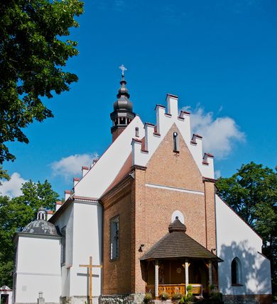 Zdjęcie nr 2: Kościół jest usytuowany w centrum wsi Rudawa, na północ od głównej drogi z Zabierzowa do Chrzanowa. Teren wokół niego jest otoczony wysokim, kamiennym murem z nieregularnych ciosów kamienia, oszkarpowanym, tynkowanym, z wyjątkiem zewnętrznej części muru na zachód od południowej bramki. W murze znajdują się trzy wejścia, od wschodu, południa i zachodu. W części wschodniej muru znajduje się trójosiowa brama wjazdowa, zwieńczona łukiem wklęsło-wypukłym, z trzema przelotami: środkowym wyższym i szerszym, zamkniętym łukiem odcinkowym i bocznymi węższymi i niższymi, zamkniętymi łukiem półkolistym (północne zamurowane). Część środkowa jest flankowana zdwojonymi pilastrami, podtrzymującymi profilowane uskokowe belkowanie z przyczółkiem o profilowanym łuku falistym, zwieńczonym równoramiennym krzyżem. W przyczółku wnęka z figurą św. Floriana. Bramki od strony zachodniej i południowej prostokątne, z przejściem zakończonym płaskim łukiem odcinkowym, z profilowanym gzymsem, zwieńczonym trójkątnym przyczółkiem. Przejścia zamykane drewnianymi ażurowymi i pomalowanymi na ciemnobrązowo jednoskrzydłowymi drzwiami. Poprzez bramkę od zachodu zejście kamiennymi schodami poprowadzonymi wzdłuż muru na dziedziniec plebański, usytuowany poniżej terenu kościelnego. 
W północno-wschodnim narożniku muru niewielka murowana i tynkowana kostnica na planie kwadratu, nakryta dachem namiotowym, łamanym, zakończonym ośmioboczną ślepą latarnią.

Po stronie południowej, poniżej placu kościelnego, do muru przylega murowana, tynkowana, prostokątna i dwukondygnacyjna „zegarowa” wieża bramna nakryta namiotowym dachem z wysoką drewnianą ośmioboczną latarnią o cebulastym hełmie. W wieży znajduje się przejazd wiodący na dziedziniec plebański, z sienią otwartą na przestrzał w dolnej kondygnacji i z lamusem dostępnym od strony placu kościelnego w górnej. 

W południowej części muru, w pobliżu południowo-wschodniego narożnika placu kościelnego, nadbudowana kamienna dzwonnica parawanowa z zawieszonymi czterema dzwonami.  

We wschodniej części placu kościelnego pomiędzy bramką wschodnią a kostnicą znajduje się kamienna ambona, o ośmiobocznej podstawie przechodzącej w szerszy, również ośmioboczny korpus, zakończony kamiennym parapetem, z kamiennymi schodami prowadzącymi na ambonę od strony wschodniej. 

Kościół jest orientowany, prawie w całości zbudowany z cegły, otynkowany z wyjątkiem prezbiterium. Wnętrze kościoła tworzy niewielkie, prostokątne, jednoprzęsłowe prezbiterium zakończone prostą ścianą i nakryte pozornym sklepieniem krzyżowo-żebrowym. Nawa jest szersza, prawie kwadratowa, nakryta drewnianym stropem. Prezbiterium z nawą są połączone szeroką, ostrołukową arkadą w ścianie tęczowej. Od północy do prezbiterium przylega założona na planie prostokąta dwuprzęsłowa zakrystia, nakryta sklepieniem krzyżowym. Wejście do zakrystii zaznaczone gotyckim, kamiennym, sfazowanym portalem zamkniętym łukiem ostrym. Od zachodu do zakrystii przylega niewielkie pomieszczenie gospodarcze, do którego z zakrystii prowadzą ostrołukowe drzwi. Zakrystia oświetlona ostrołukowym oknem w ścianie wschodniej, wypełnionym witrażem z tafelek w kształcie sześciokąta foremnego, ze szkła surowego, tzw. katedralnego. 

Od południa do nawy przylega kaplica o formach renesansowych, dwukondygnacyjna, założona na planie kwadratu. W dolnej kondygnacji sklepiona krzyżowo-żebrowo kruchta otwarta do nawy szeroką, zamkniętą półkoliście arkadą.

Ponad kruchtą kaplica św. Kazimierza, nakryta wspartą na pendentywach kopułą z latarnią. Z kruchty do kaplicy prowadzą kręte kamienne schody umieszczone od zachodu w półkolistej wieżyczce. Prostokątne wejście z krypty na klatkę schodową ujęte kamiennym profilowanym portalem. Kaplica otwarta do nawy szeroką, zamkniętą półkoliście arkadą, o kształcie i wymiarach analogicznych do arkady znajdującej się poniżej. Kaplicę, prócz latarni, oświetla prostokątne okno w ścianie południowej, wypełnione witrażem z tafelek w kształcie gomółek, ze szkła surowego, tzw. katedralnego. Na zachodniej ścianie nawy chór muzyczny, dostępny klatką schodową ukrytą w zewnętrznym aneksie przylegającym do zachodniej elewacji nawy i południowej elewacji wieży-dzwonnicy. 

Nawę i prezbiterium oświetlają umieszczone w południowych ścianach prostokątne, rozglifione okna: jedno w prezbiterium, dwa w nawie. Wszystkie wypełnione witrażami z tafelek w kształcie gomółek, ze szkła surowego, tzw. katedralnego. 

Do kościoła prowadzą dwa wejścia: poprzez arkadę z kruchty południowej oraz szerokie wejście główne prostokątne, zamknięte łukiem odcinkowym, prowadzące do kościoła z obszernej kruchty od strony zachodniej, znajdującej się w murowanym przyziemiu wieży - dzwonnicy. Kruchta, założona na planie kwadratu i nakryta murowanym stropem, doświetlona jest dwoma prostokątnymi oknami umieszczonymi naprzeciw siebie w ścianach północnej i południowej.
 
W zewnętrznej elewacji kościoła widoczny niewysoki kamienny cokół wykonany z nieregularnych ciosów kamienia. Prezbiterium, niższe od nawy, murowane z cegły w układzie wedyjskim, z domieszką układu polskiego. Wschodnie naroża prezbiterium zaakcentowane płaskimi lizenami. We wschodniej ścianie widoczny zarys zamurowanego wydłużonego okna zamkniętego lekko zaostrzonym łukiem, w trójkątnym szczycie znajduje się niewielkie wąskie okienko zakończone łukiem półkolistym. Południowa ściana prezbiterium ozdobiona fryzem z cegieł. Do ściany północnej prezbiterium przylega zakrystia, oszkarpowana, nakryta dachem pulpitowym, z dobudowanym od niej niewielkim aneksem, nakrytym takim samym zadaszeniem. Do wschodniej ściany prezbiterium przylega ogrójec nakryty dachem namiotowym z cebulastym zwieńczeniem, wspartym na sześciu smukłych, profilowanych drewnianych słupach z mieczami, pomiędzy którymi od północy i południa ażurowa drewniana balustrada. 

Nawa oszkarpowana w narożnikach. Elewacje bez podziałów architektonicznych. Od strony południowej do nawy dobudowana dwukondygnacyjna kaplica nakryta kopułą z latarnią, podzielona na dwie kondygnacje. W dolnej kondygnacji od południa wejście do kruchty zaznaczone kamiennym portalem o sfazowanych węgarach i lekko zaostrzonym łuku. Wejście zamykają drewniane dwuskrzydłowe drzwi ozdobione kratownicą z żelaznych listew. Od zachodu do kaplicy przylega półokrągła wieżyczka nakryta daszkiem stożkowym. 

Do zachodniej fasady kościoła dostawiona niska, założona na planie kwadratu trójkondygnacyjna wieża-dzwonnica: w dolnej części murowana, w narożach wzmocniona kamiennymi szkarpami, w górnej drewniana konstrukcji słupowo-ramowej z nadwieszoną izbicą i nakryta dachem półszczytowym. W dolnej, murowanej kondygnacji, na osi kościoła, prostokątne wejście do kruchty zaakcentowane przedsionkiem w kształcie ostrołukowej arkady i czterostopniowymi schodami. Przedsionek nakryty dachem dwuspadowym. Do zachodniej elewacji nawy i południowej elewacji dzwonnicy przylega niewielki, wysoki drewniany aneks, nakryty dachem pulpitowym, mieszczący klatkę schodową prowadzącą na górną kondygnację dzwonnicy i na chór muzyczny w nawie kościoła. Prostokątne wejście w południowej ścianie aneksu, do którego prowadzą pięciostopniowe proste schody. Ponad nimi, na wysokości drugiej kondygnacji dzwonnicy, niewielkie kwadratowe okno. 

Prezbiterium i nawa przykryte stromymi dachami dwuspadowymi, zamkniętymi od wschodu i zachodu szczytami sterczynowymi. Wieżyczka na sygnaturkę ośmioboczna, w dolnej części barokowa, w górnej części nowsza.