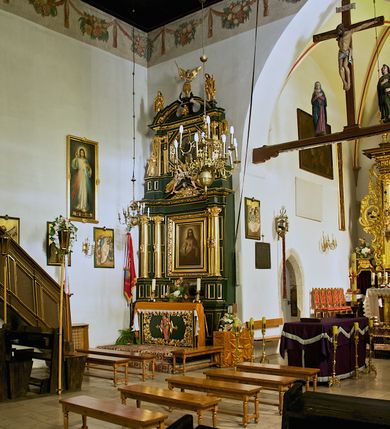 Zdjęcie nr 29: Kościół jest usytuowany w centrum wsi Rudawa, na północ od głównej drogi z Zabierzowa do Chrzanowa. Teren wokół niego jest otoczony wysokim, kamiennym murem z nieregularnych ciosów kamienia, oszkarpowanym, tynkowanym, z wyjątkiem zewnętrznej części muru na zachód od południowej bramki. W murze znajdują się trzy wejścia, od wschodu, południa i zachodu. W części wschodniej muru znajduje się trójosiowa brama wjazdowa, zwieńczona łukiem wklęsło-wypukłym, z trzema przelotami: środkowym wyższym i szerszym, zamkniętym łukiem odcinkowym i bocznymi węższymi i niższymi, zamkniętymi łukiem półkolistym (północne zamurowane). Część środkowa jest flankowana zdwojonymi pilastrami, podtrzymującymi profilowane uskokowe belkowanie z przyczółkiem o profilowanym łuku falistym, zwieńczonym równoramiennym krzyżem. W przyczółku wnęka z figurą św. Floriana. Bramki od strony zachodniej i południowej prostokątne, z przejściem zakończonym płaskim łukiem odcinkowym, z profilowanym gzymsem, zwieńczonym trójkątnym przyczółkiem. Przejścia zamykane drewnianymi ażurowymi i pomalowanymi na ciemnobrązowo jednoskrzydłowymi drzwiami. Poprzez bramkę od zachodu zejście kamiennymi schodami poprowadzonymi wzdłuż muru na dziedziniec plebański, usytuowany poniżej terenu kościelnego. 
W północno-wschodnim narożniku muru niewielka murowana i tynkowana kostnica na planie kwadratu, nakryta dachem namiotowym, łamanym, zakończonym ośmioboczną ślepą latarnią.

Po stronie południowej, poniżej placu kościelnego, do muru przylega murowana, tynkowana, prostokątna i dwukondygnacyjna „zegarowa” wieża bramna nakryta namiotowym dachem z wysoką drewnianą ośmioboczną latarnią o cebulastym hełmie. W wieży znajduje się przejazd wiodący na dziedziniec plebański, z sienią otwartą na przestrzał w dolnej kondygnacji i z lamusem dostępnym od strony placu kościelnego w górnej. 

W południowej części muru, w pobliżu południowo-wschodniego narożnika placu kościelnego, nadbudowana kamienna dzwonnica parawanowa z zawieszonymi czterema dzwonami.  

We wschodniej części placu kościelnego pomiędzy bramką wschodnią a kostnicą znajduje się kamienna ambona, o ośmiobocznej podstawie przechodzącej w szerszy, również ośmioboczny korpus, zakończony kamiennym parapetem, z kamiennymi schodami prowadzącymi na ambonę od strony wschodniej. 

Kościół jest orientowany, prawie w całości zbudowany z cegły, otynkowany z wyjątkiem prezbiterium. Wnętrze kościoła tworzy niewielkie, prostokątne, jednoprzęsłowe prezbiterium zakończone prostą ścianą i nakryte pozornym sklepieniem krzyżowo-żebrowym. Nawa jest szersza, prawie kwadratowa, nakryta drewnianym stropem. Prezbiterium z nawą są połączone szeroką, ostrołukową arkadą w ścianie tęczowej. Od północy do prezbiterium przylega założona na planie prostokąta dwuprzęsłowa zakrystia, nakryta sklepieniem krzyżowym. Wejście do zakrystii zaznaczone gotyckim, kamiennym, sfazowanym portalem zamkniętym łukiem ostrym. Od zachodu do zakrystii przylega niewielkie pomieszczenie gospodarcze, do którego z zakrystii prowadzą ostrołukowe drzwi. Zakrystia oświetlona ostrołukowym oknem w ścianie wschodniej, wypełnionym witrażem z tafelek w kształcie sześciokąta foremnego, ze szkła surowego, tzw. katedralnego. 

Od południa do nawy przylega kaplica o formach renesansowych, dwukondygnacyjna, założona na planie kwadratu. W dolnej kondygnacji sklepiona krzyżowo-żebrowo kruchta otwarta do nawy szeroką, zamkniętą półkoliście arkadą.

Ponad kruchtą kaplica św. Kazimierza, nakryta wspartą na pendentywach kopułą z latarnią. Z kruchty do kaplicy prowadzą kręte kamienne schody umieszczone od zachodu w półkolistej wieżyczce. Prostokątne wejście z krypty na klatkę schodową ujęte kamiennym profilowanym portalem. Kaplica otwarta do nawy szeroką, zamkniętą półkoliście arkadą, o kształcie i wymiarach analogicznych do arkady znajdującej się poniżej. Kaplicę, prócz latarni, oświetla prostokątne okno w ścianie południowej, wypełnione witrażem z tafelek w kształcie gomółek, ze szkła surowego, tzw. katedralnego. Na zachodniej ścianie nawy chór muzyczny, dostępny klatką schodową ukrytą w zewnętrznym aneksie przylegającym do zachodniej elewacji nawy i południowej elewacji wieży-dzwonnicy. 

Nawę i prezbiterium oświetlają umieszczone w południowych ścianach prostokątne, rozglifione okna: jedno w prezbiterium, dwa w nawie. Wszystkie wypełnione witrażami z tafelek w kształcie gomółek, ze szkła surowego, tzw. katedralnego. 

Do kościoła prowadzą dwa wejścia: poprzez arkadę z kruchty południowej oraz szerokie wejście główne prostokątne, zamknięte łukiem odcinkowym, prowadzące do kościoła z obszernej kruchty od strony zachodniej, znajdującej się w murowanym przyziemiu wieży - dzwonnicy. Kruchta, założona na planie kwadratu i nakryta murowanym stropem, doświetlona jest dwoma prostokątnymi oknami umieszczonymi naprzeciw siebie w ścianach północnej i południowej.
 
W zewnętrznej elewacji kościoła widoczny niewysoki kamienny cokół wykonany z nieregularnych ciosów kamienia. Prezbiterium, niższe od nawy, murowane z cegły w układzie wedyjskim, z domieszką układu polskiego. Wschodnie naroża prezbiterium zaakcentowane płaskimi lizenami. We wschodniej ścianie widoczny zarys zamurowanego wydłużonego okna zamkniętego lekko zaostrzonym łukiem, w trójkątnym szczycie znajduje się niewielkie wąskie okienko zakończone łukiem półkolistym. Południowa ściana prezbiterium ozdobiona fryzem z cegieł. Do ściany północnej prezbiterium przylega zakrystia, oszkarpowana, nakryta dachem pulpitowym, z dobudowanym od niej niewielkim aneksem, nakrytym takim samym zadaszeniem. Do wschodniej ściany prezbiterium przylega ogrójec nakryty dachem namiotowym z cebulastym zwieńczeniem, wspartym na sześciu smukłych, profilowanych drewnianych słupach z mieczami, pomiędzy którymi od północy i południa ażurowa drewniana balustrada. 

Nawa oszkarpowana w narożnikach. Elewacje bez podziałów architektonicznych. Od strony południowej do nawy dobudowana dwukondygnacyjna kaplica nakryta kopułą z latarnią, podzielona na dwie kondygnacje. W dolnej kondygnacji od południa wejście do kruchty zaznaczone kamiennym portalem o sfazowanych węgarach i lekko zaostrzonym łuku. Wejście zamykają drewniane dwuskrzydłowe drzwi ozdobione kratownicą z żelaznych listew. Od zachodu do kaplicy przylega półokrągła wieżyczka nakryta daszkiem stożkowym. 

Do zachodniej fasady kościoła dostawiona niska, założona na planie kwadratu trójkondygnacyjna wieża-dzwonnica: w dolnej części murowana, w narożach wzmocniona kamiennymi szkarpami, w górnej drewniana konstrukcji słupowo-ramowej z nadwieszoną izbicą i nakryta dachem półszczytowym. W dolnej, murowanej kondygnacji, na osi kościoła, prostokątne wejście do kruchty zaakcentowane przedsionkiem w kształcie ostrołukowej arkady i czterostopniowymi schodami. Przedsionek nakryty dachem dwuspadowym. Do zachodniej elewacji nawy i południowej elewacji dzwonnicy przylega niewielki, wysoki drewniany aneks, nakryty dachem pulpitowym, mieszczący klatkę schodową prowadzącą na górną kondygnację dzwonnicy i na chór muzyczny w nawie kościoła. Prostokątne wejście w południowej ścianie aneksu, do którego prowadzą pięciostopniowe proste schody. Ponad nimi, na wysokości drugiej kondygnacji dzwonnicy, niewielkie kwadratowe okno. 

Prezbiterium i nawa przykryte stromymi dachami dwuspadowymi, zamkniętymi od wschodu i zachodu szczytami sterczynowymi. Wieżyczka na sygnaturkę ośmioboczna, w dolnej części barokowa, w górnej części nowsza.