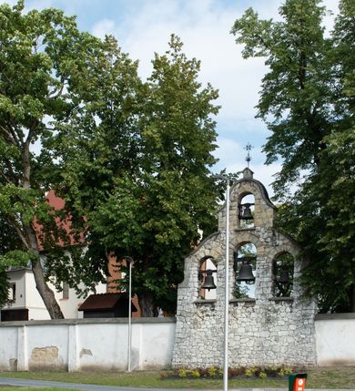 Zdjęcie nr 24: Kościół jest usytuowany w centrum wsi Rudawa, na północ od głównej drogi z Zabierzowa do Chrzanowa. Teren wokół niego jest otoczony wysokim, kamiennym murem z nieregularnych ciosów kamienia, oszkarpowanym, tynkowanym, z wyjątkiem zewnętrznej części muru na zachód od południowej bramki. W murze znajdują się trzy wejścia, od wschodu, południa i zachodu. W części wschodniej muru znajduje się trójosiowa brama wjazdowa, zwieńczona łukiem wklęsło-wypukłym, z trzema przelotami: środkowym wyższym i szerszym, zamkniętym łukiem odcinkowym i bocznymi węższymi i niższymi, zamkniętymi łukiem półkolistym (północne zamurowane). Część środkowa jest flankowana zdwojonymi pilastrami, podtrzymującymi profilowane uskokowe belkowanie z przyczółkiem o profilowanym łuku falistym, zwieńczonym równoramiennym krzyżem. W przyczółku wnęka z figurą św. Floriana. Bramki od strony zachodniej i południowej prostokątne, z przejściem zakończonym płaskim łukiem odcinkowym, z profilowanym gzymsem, zwieńczonym trójkątnym przyczółkiem. Przejścia zamykane drewnianymi ażurowymi i pomalowanymi na ciemnobrązowo jednoskrzydłowymi drzwiami. Poprzez bramkę od zachodu zejście kamiennymi schodami poprowadzonymi wzdłuż muru na dziedziniec plebański, usytuowany poniżej terenu kościelnego. 
W północno-wschodnim narożniku muru niewielka murowana i tynkowana kostnica na planie kwadratu, nakryta dachem namiotowym, łamanym, zakończonym ośmioboczną ślepą latarnią.

Po stronie południowej, poniżej placu kościelnego, do muru przylega murowana, tynkowana, prostokątna i dwukondygnacyjna „zegarowa” wieża bramna nakryta namiotowym dachem z wysoką drewnianą ośmioboczną latarnią o cebulastym hełmie. W wieży znajduje się przejazd wiodący na dziedziniec plebański, z sienią otwartą na przestrzał w dolnej kondygnacji i z lamusem dostępnym od strony placu kościelnego w górnej. 

W południowej części muru, w pobliżu południowo-wschodniego narożnika placu kościelnego, nadbudowana kamienna dzwonnica parawanowa z zawieszonymi czterema dzwonami.  

We wschodniej części placu kościelnego pomiędzy bramką wschodnią a kostnicą znajduje się kamienna ambona, o ośmiobocznej podstawie przechodzącej w szerszy, również ośmioboczny korpus, zakończony kamiennym parapetem, z kamiennymi schodami prowadzącymi na ambonę od strony wschodniej. 

Kościół jest orientowany, prawie w całości zbudowany z cegły, otynkowany z wyjątkiem prezbiterium. Wnętrze kościoła tworzy niewielkie, prostokątne, jednoprzęsłowe prezbiterium zakończone prostą ścianą i nakryte pozornym sklepieniem krzyżowo-żebrowym. Nawa jest szersza, prawie kwadratowa, nakryta drewnianym stropem. Prezbiterium z nawą są połączone szeroką, ostrołukową arkadą w ścianie tęczowej. Od północy do prezbiterium przylega założona na planie prostokąta dwuprzęsłowa zakrystia, nakryta sklepieniem krzyżowym. Wejście do zakrystii zaznaczone gotyckim, kamiennym, sfazowanym portalem zamkniętym łukiem ostrym. Od zachodu do zakrystii przylega niewielkie pomieszczenie gospodarcze, do którego z zakrystii prowadzą ostrołukowe drzwi. Zakrystia oświetlona ostrołukowym oknem w ścianie wschodniej, wypełnionym witrażem z tafelek w kształcie sześciokąta foremnego, ze szkła surowego, tzw. katedralnego. 

Od południa do nawy przylega kaplica o formach renesansowych, dwukondygnacyjna, założona na planie kwadratu. W dolnej kondygnacji sklepiona krzyżowo-żebrowo kruchta otwarta do nawy szeroką, zamkniętą półkoliście arkadą.

Ponad kruchtą kaplica św. Kazimierza, nakryta wspartą na pendentywach kopułą z latarnią. Z kruchty do kaplicy prowadzą kręte kamienne schody umieszczone od zachodu w półkolistej wieżyczce. Prostokątne wejście z krypty na klatkę schodową ujęte kamiennym profilowanym portalem. Kaplica otwarta do nawy szeroką, zamkniętą półkoliście arkadą, o kształcie i wymiarach analogicznych do arkady znajdującej się poniżej. Kaplicę, prócz latarni, oświetla prostokątne okno w ścianie południowej, wypełnione witrażem z tafelek w kształcie gomółek, ze szkła surowego, tzw. katedralnego. Na zachodniej ścianie nawy chór muzyczny, dostępny klatką schodową ukrytą w zewnętrznym aneksie przylegającym do zachodniej elewacji nawy i południowej elewacji wieży-dzwonnicy. 

Nawę i prezbiterium oświetlają umieszczone w południowych ścianach prostokątne, rozglifione okna: jedno w prezbiterium, dwa w nawie. Wszystkie wypełnione witrażami z tafelek w kształcie gomółek, ze szkła surowego, tzw. katedralnego. 

Do kościoła prowadzą dwa wejścia: poprzez arkadę z kruchty południowej oraz szerokie wejście główne prostokątne, zamknięte łukiem odcinkowym, prowadzące do kościoła z obszernej kruchty od strony zachodniej, znajdującej się w murowanym przyziemiu wieży - dzwonnicy. Kruchta, założona na planie kwadratu i nakryta murowanym stropem, doświetlona jest dwoma prostokątnymi oknami umieszczonymi naprzeciw siebie w ścianach północnej i południowej.
 
W zewnętrznej elewacji kościoła widoczny niewysoki kamienny cokół wykonany z nieregularnych ciosów kamienia. Prezbiterium, niższe od nawy, murowane z cegły w układzie wedyjskim, z domieszką układu polskiego. Wschodnie naroża prezbiterium zaakcentowane płaskimi lizenami. We wschodniej ścianie widoczny zarys zamurowanego wydłużonego okna zamkniętego lekko zaostrzonym łukiem, w trójkątnym szczycie znajduje się niewielkie wąskie okienko zakończone łukiem półkolistym. Południowa ściana prezbiterium ozdobiona fryzem z cegieł. Do ściany północnej prezbiterium przylega zakrystia, oszkarpowana, nakryta dachem pulpitowym, z dobudowanym od niej niewielkim aneksem, nakrytym takim samym zadaszeniem. Do wschodniej ściany prezbiterium przylega ogrójec nakryty dachem namiotowym z cebulastym zwieńczeniem, wspartym na sześciu smukłych, profilowanych drewnianych słupach z mieczami, pomiędzy którymi od północy i południa ażurowa drewniana balustrada. 

Nawa oszkarpowana w narożnikach. Elewacje bez podziałów architektonicznych. Od strony południowej do nawy dobudowana dwukondygnacyjna kaplica nakryta kopułą z latarnią, podzielona na dwie kondygnacje. W dolnej kondygnacji od południa wejście do kruchty zaznaczone kamiennym portalem o sfazowanych węgarach i lekko zaostrzonym łuku. Wejście zamykają drewniane dwuskrzydłowe drzwi ozdobione kratownicą z żelaznych listew. Od zachodu do kaplicy przylega półokrągła wieżyczka nakryta daszkiem stożkowym. 

Do zachodniej fasady kościoła dostawiona niska, założona na planie kwadratu trójkondygnacyjna wieża-dzwonnica: w dolnej części murowana, w narożach wzmocniona kamiennymi szkarpami, w górnej drewniana konstrukcji słupowo-ramowej z nadwieszoną izbicą i nakryta dachem półszczytowym. W dolnej, murowanej kondygnacji, na osi kościoła, prostokątne wejście do kruchty zaakcentowane przedsionkiem w kształcie ostrołukowej arkady i czterostopniowymi schodami. Przedsionek nakryty dachem dwuspadowym. Do zachodniej elewacji nawy i południowej elewacji dzwonnicy przylega niewielki, wysoki drewniany aneks, nakryty dachem pulpitowym, mieszczący klatkę schodową prowadzącą na górną kondygnację dzwonnicy i na chór muzyczny w nawie kościoła. Prostokątne wejście w południowej ścianie aneksu, do którego prowadzą pięciostopniowe proste schody. Ponad nimi, na wysokości drugiej kondygnacji dzwonnicy, niewielkie kwadratowe okno. 

Prezbiterium i nawa przykryte stromymi dachami dwuspadowymi, zamkniętymi od wschodu i zachodu szczytami sterczynowymi. Wieżyczka na sygnaturkę ośmioboczna, w dolnej części barokowa, w górnej części nowsza.