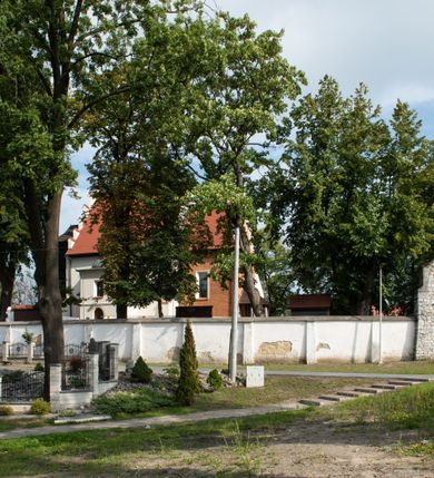 Zdjęcie nr 13: Kościół jest usytuowany w centrum wsi Rudawa, na północ od głównej drogi z Zabierzowa do Chrzanowa. Teren wokół niego jest otoczony wysokim, kamiennym murem z nieregularnych ciosów kamienia, oszkarpowanym, tynkowanym, z wyjątkiem zewnętrznej części muru na zachód od południowej bramki. W murze znajdują się trzy wejścia, od wschodu, południa i zachodu. W części wschodniej muru znajduje się trójosiowa brama wjazdowa, zwieńczona łukiem wklęsło-wypukłym, z trzema przelotami: środkowym wyższym i szerszym, zamkniętym łukiem odcinkowym i bocznymi węższymi i niższymi, zamkniętymi łukiem półkolistym (północne zamurowane). Część środkowa jest flankowana zdwojonymi pilastrami, podtrzymującymi profilowane uskokowe belkowanie z przyczółkiem o profilowanym łuku falistym, zwieńczonym równoramiennym krzyżem. W przyczółku wnęka z figurą św. Floriana. Bramki od strony zachodniej i południowej prostokątne, z przejściem zakończonym płaskim łukiem odcinkowym, z profilowanym gzymsem, zwieńczonym trójkątnym przyczółkiem. Przejścia zamykane drewnianymi ażurowymi i pomalowanymi na ciemnobrązowo jednoskrzydłowymi drzwiami. Poprzez bramkę od zachodu zejście kamiennymi schodami poprowadzonymi wzdłuż muru na dziedziniec plebański, usytuowany poniżej terenu kościelnego. 
W północno-wschodnim narożniku muru niewielka murowana i tynkowana kostnica na planie kwadratu, nakryta dachem namiotowym, łamanym, zakończonym ośmioboczną ślepą latarnią.

Po stronie południowej, poniżej placu kościelnego, do muru przylega murowana, tynkowana, prostokątna i dwukondygnacyjna „zegarowa” wieża bramna nakryta namiotowym dachem z wysoką drewnianą ośmioboczną latarnią o cebulastym hełmie. W wieży znajduje się przejazd wiodący na dziedziniec plebański, z sienią otwartą na przestrzał w dolnej kondygnacji i z lamusem dostępnym od strony placu kościelnego w górnej. 

W południowej części muru, w pobliżu południowo-wschodniego narożnika placu kościelnego, nadbudowana kamienna dzwonnica parawanowa z zawieszonymi czterema dzwonami.  

We wschodniej części placu kościelnego pomiędzy bramką wschodnią a kostnicą znajduje się kamienna ambona, o ośmiobocznej podstawie przechodzącej w szerszy, również ośmioboczny korpus, zakończony kamiennym parapetem, z kamiennymi schodami prowadzącymi na ambonę od strony wschodniej. 

Kościół jest orientowany, prawie w całości zbudowany z cegły, otynkowany z wyjątkiem prezbiterium. Wnętrze kościoła tworzy niewielkie, prostokątne, jednoprzęsłowe prezbiterium zakończone prostą ścianą i nakryte pozornym sklepieniem krzyżowo-żebrowym. Nawa jest szersza, prawie kwadratowa, nakryta drewnianym stropem. Prezbiterium z nawą są połączone szeroką, ostrołukową arkadą w ścianie tęczowej. Od północy do prezbiterium przylega założona na planie prostokąta dwuprzęsłowa zakrystia, nakryta sklepieniem krzyżowym. Wejście do zakrystii zaznaczone gotyckim, kamiennym, sfazowanym portalem zamkniętym łukiem ostrym. Od zachodu do zakrystii przylega niewielkie pomieszczenie gospodarcze, do którego z zakrystii prowadzą ostrołukowe drzwi. Zakrystia oświetlona ostrołukowym oknem w ścianie wschodniej, wypełnionym witrażem z tafelek w kształcie sześciokąta foremnego, ze szkła surowego, tzw. katedralnego. 

Od południa do nawy przylega kaplica o formach renesansowych, dwukondygnacyjna, założona na planie kwadratu. W dolnej kondygnacji sklepiona krzyżowo-żebrowo kruchta otwarta do nawy szeroką, zamkniętą półkoliście arkadą.

Ponad kruchtą kaplica św. Kazimierza, nakryta wspartą na pendentywach kopułą z latarnią. Z kruchty do kaplicy prowadzą kręte kamienne schody umieszczone od zachodu w półkolistej wieżyczce. Prostokątne wejście z krypty na klatkę schodową ujęte kamiennym profilowanym portalem. Kaplica otwarta do nawy szeroką, zamkniętą półkoliście arkadą, o kształcie i wymiarach analogicznych do arkady znajdującej się poniżej. Kaplicę, prócz latarni, oświetla prostokątne okno w ścianie południowej, wypełnione witrażem z tafelek w kształcie gomółek, ze szkła surowego, tzw. katedralnego. Na zachodniej ścianie nawy chór muzyczny, dostępny klatką schodową ukrytą w zewnętrznym aneksie przylegającym do zachodniej elewacji nawy i południowej elewacji wieży-dzwonnicy. 

Nawę i prezbiterium oświetlają umieszczone w południowych ścianach prostokątne, rozglifione okna: jedno w prezbiterium, dwa w nawie. Wszystkie wypełnione witrażami z tafelek w kształcie gomółek, ze szkła surowego, tzw. katedralnego. 

Do kościoła prowadzą dwa wejścia: poprzez arkadę z kruchty południowej oraz szerokie wejście główne prostokątne, zamknięte łukiem odcinkowym, prowadzące do kościoła z obszernej kruchty od strony zachodniej, znajdującej się w murowanym przyziemiu wieży - dzwonnicy. Kruchta, założona na planie kwadratu i nakryta murowanym stropem, doświetlona jest dwoma prostokątnymi oknami umieszczonymi naprzeciw siebie w ścianach północnej i południowej.
 
W zewnętrznej elewacji kościoła widoczny niewysoki kamienny cokół wykonany z nieregularnych ciosów kamienia. Prezbiterium, niższe od nawy, murowane z cegły w układzie wedyjskim, z domieszką układu polskiego. Wschodnie naroża prezbiterium zaakcentowane płaskimi lizenami. We wschodniej ścianie widoczny zarys zamurowanego wydłużonego okna zamkniętego lekko zaostrzonym łukiem, w trójkątnym szczycie znajduje się niewielkie wąskie okienko zakończone łukiem półkolistym. Południowa ściana prezbiterium ozdobiona fryzem z cegieł. Do ściany północnej prezbiterium przylega zakrystia, oszkarpowana, nakryta dachem pulpitowym, z dobudowanym od niej niewielkim aneksem, nakrytym takim samym zadaszeniem. Do wschodniej ściany prezbiterium przylega ogrójec nakryty dachem namiotowym z cebulastym zwieńczeniem, wspartym na sześciu smukłych, profilowanych drewnianych słupach z mieczami, pomiędzy którymi od północy i południa ażurowa drewniana balustrada. 

Nawa oszkarpowana w narożnikach. Elewacje bez podziałów architektonicznych. Od strony południowej do nawy dobudowana dwukondygnacyjna kaplica nakryta kopułą z latarnią, podzielona na dwie kondygnacje. W dolnej kondygnacji od południa wejście do kruchty zaznaczone kamiennym portalem o sfazowanych węgarach i lekko zaostrzonym łuku. Wejście zamykają drewniane dwuskrzydłowe drzwi ozdobione kratownicą z żelaznych listew. Od zachodu do kaplicy przylega półokrągła wieżyczka nakryta daszkiem stożkowym. 

Do zachodniej fasady kościoła dostawiona niska, założona na planie kwadratu trójkondygnacyjna wieża-dzwonnica: w dolnej części murowana, w narożach wzmocniona kamiennymi szkarpami, w górnej drewniana konstrukcji słupowo-ramowej z nadwieszoną izbicą i nakryta dachem półszczytowym. W dolnej, murowanej kondygnacji, na osi kościoła, prostokątne wejście do kruchty zaakcentowane przedsionkiem w kształcie ostrołukowej arkady i czterostopniowymi schodami. Przedsionek nakryty dachem dwuspadowym. Do zachodniej elewacji nawy i południowej elewacji dzwonnicy przylega niewielki, wysoki drewniany aneks, nakryty dachem pulpitowym, mieszczący klatkę schodową prowadzącą na górną kondygnację dzwonnicy i na chór muzyczny w nawie kościoła. Prostokątne wejście w południowej ścianie aneksu, do którego prowadzą pięciostopniowe proste schody. Ponad nimi, na wysokości drugiej kondygnacji dzwonnicy, niewielkie kwadratowe okno. 

Prezbiterium i nawa przykryte stromymi dachami dwuspadowymi, zamkniętymi od wschodu i zachodu szczytami sterczynowymi. Wieżyczka na sygnaturkę ośmioboczna, w dolnej części barokowa, w górnej części nowsza.
