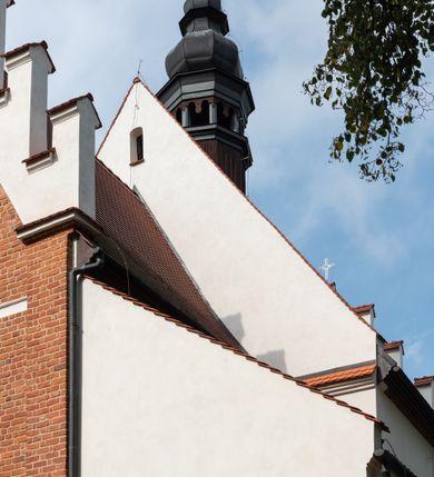 Zdjęcie nr 6: Kościół jest usytuowany w centrum wsi Rudawa, na północ od głównej drogi z Zabierzowa do Chrzanowa. Teren wokół niego jest otoczony wysokim, kamiennym murem z nieregularnych ciosów kamienia, oszkarpowanym, tynkowanym, z wyjątkiem zewnętrznej części muru na zachód od południowej bramki. W murze znajdują się trzy wejścia, od wschodu, południa i zachodu. W części wschodniej muru znajduje się trójosiowa brama wjazdowa, zwieńczona łukiem wklęsło-wypukłym, z trzema przelotami: środkowym wyższym i szerszym, zamkniętym łukiem odcinkowym i bocznymi węższymi i niższymi, zamkniętymi łukiem półkolistym (północne zamurowane). Część środkowa jest flankowana zdwojonymi pilastrami, podtrzymującymi profilowane uskokowe belkowanie z przyczółkiem o profilowanym łuku falistym, zwieńczonym równoramiennym krzyżem. W przyczółku wnęka z figurą św. Floriana. Bramki od strony zachodniej i południowej prostokątne, z przejściem zakończonym płaskim łukiem odcinkowym, z profilowanym gzymsem, zwieńczonym trójkątnym przyczółkiem. Przejścia zamykane drewnianymi ażurowymi i pomalowanymi na ciemnobrązowo jednoskrzydłowymi drzwiami. Poprzez bramkę od zachodu zejście kamiennymi schodami poprowadzonymi wzdłuż muru na dziedziniec plebański, usytuowany poniżej terenu kościelnego. 
W północno-wschodnim narożniku muru niewielka murowana i tynkowana kostnica na planie kwadratu, nakryta dachem namiotowym, łamanym, zakończonym ośmioboczną ślepą latarnią.

Po stronie południowej, poniżej placu kościelnego, do muru przylega murowana, tynkowana, prostokątna i dwukondygnacyjna „zegarowa” wieża bramna nakryta namiotowym dachem z wysoką drewnianą ośmioboczną latarnią o cebulastym hełmie. W wieży znajduje się przejazd wiodący na dziedziniec plebański, z sienią otwartą na przestrzał w dolnej kondygnacji i z lamusem dostępnym od strony placu kościelnego w górnej. 

W południowej części muru, w pobliżu południowo-wschodniego narożnika placu kościelnego, nadbudowana kamienna dzwonnica parawanowa z zawieszonymi czterema dzwonami.  

We wschodniej części placu kościelnego pomiędzy bramką wschodnią a kostnicą znajduje się kamienna ambona, o ośmiobocznej podstawie przechodzącej w szerszy, również ośmioboczny korpus, zakończony kamiennym parapetem, z kamiennymi schodami prowadzącymi na ambonę od strony wschodniej. 

Kościół jest orientowany, prawie w całości zbudowany z cegły, otynkowany z wyjątkiem prezbiterium. Wnętrze kościoła tworzy niewielkie, prostokątne, jednoprzęsłowe prezbiterium zakończone prostą ścianą i nakryte pozornym sklepieniem krzyżowo-żebrowym. Nawa jest szersza, prawie kwadratowa, nakryta drewnianym stropem. Prezbiterium z nawą są połączone szeroką, ostrołukową arkadą w ścianie tęczowej. Od północy do prezbiterium przylega założona na planie prostokąta dwuprzęsłowa zakrystia, nakryta sklepieniem krzyżowym. Wejście do zakrystii zaznaczone gotyckim, kamiennym, sfazowanym portalem zamkniętym łukiem ostrym. Od zachodu do zakrystii przylega niewielkie pomieszczenie gospodarcze, do którego z zakrystii prowadzą ostrołukowe drzwi. Zakrystia oświetlona ostrołukowym oknem w ścianie wschodniej, wypełnionym witrażem z tafelek w kształcie sześciokąta foremnego, ze szkła surowego, tzw. katedralnego. 

Od południa do nawy przylega kaplica o formach renesansowych, dwukondygnacyjna, założona na planie kwadratu. W dolnej kondygnacji sklepiona krzyżowo-żebrowo kruchta otwarta do nawy szeroką, zamkniętą półkoliście arkadą.

Ponad kruchtą kaplica św. Kazimierza, nakryta wspartą na pendentywach kopułą z latarnią. Z kruchty do kaplicy prowadzą kręte kamienne schody umieszczone od zachodu w półkolistej wieżyczce. Prostokątne wejście z krypty na klatkę schodową ujęte kamiennym profilowanym portalem. Kaplica otwarta do nawy szeroką, zamkniętą półkoliście arkadą, o kształcie i wymiarach analogicznych do arkady znajdującej się poniżej. Kaplicę, prócz latarni, oświetla prostokątne okno w ścianie południowej, wypełnione witrażem z tafelek w kształcie gomółek, ze szkła surowego, tzw. katedralnego. Na zachodniej ścianie nawy chór muzyczny, dostępny klatką schodową ukrytą w zewnętrznym aneksie przylegającym do zachodniej elewacji nawy i południowej elewacji wieży-dzwonnicy. 

Nawę i prezbiterium oświetlają umieszczone w południowych ścianach prostokątne, rozglifione okna: jedno w prezbiterium, dwa w nawie. Wszystkie wypełnione witrażami z tafelek w kształcie gomółek, ze szkła surowego, tzw. katedralnego. 

Do kościoła prowadzą dwa wejścia: poprzez arkadę z kruchty południowej oraz szerokie wejście główne prostokątne, zamknięte łukiem odcinkowym, prowadzące do kościoła z obszernej kruchty od strony zachodniej, znajdującej się w murowanym przyziemiu wieży - dzwonnicy. Kruchta, założona na planie kwadratu i nakryta murowanym stropem, doświetlona jest dwoma prostokątnymi oknami umieszczonymi naprzeciw siebie w ścianach północnej i południowej.
 
W zewnętrznej elewacji kościoła widoczny niewysoki kamienny cokół wykonany z nieregularnych ciosów kamienia. Prezbiterium, niższe od nawy, murowane z cegły w układzie wedyjskim, z domieszką układu polskiego. Wschodnie naroża prezbiterium zaakcentowane płaskimi lizenami. We wschodniej ścianie widoczny zarys zamurowanego wydłużonego okna zamkniętego lekko zaostrzonym łukiem, w trójkątnym szczycie znajduje się niewielkie wąskie okienko zakończone łukiem półkolistym. Południowa ściana prezbiterium ozdobiona fryzem z cegieł. Do ściany północnej prezbiterium przylega zakrystia, oszkarpowana, nakryta dachem pulpitowym, z dobudowanym od niej niewielkim aneksem, nakrytym takim samym zadaszeniem. Do wschodniej ściany prezbiterium przylega ogrójec nakryty dachem namiotowym z cebulastym zwieńczeniem, wspartym na sześciu smukłych, profilowanych drewnianych słupach z mieczami, pomiędzy którymi od północy i południa ażurowa drewniana balustrada. 

Nawa oszkarpowana w narożnikach. Elewacje bez podziałów architektonicznych. Od strony południowej do nawy dobudowana dwukondygnacyjna kaplica nakryta kopułą z latarnią, podzielona na dwie kondygnacje. W dolnej kondygnacji od południa wejście do kruchty zaznaczone kamiennym portalem o sfazowanych węgarach i lekko zaostrzonym łuku. Wejście zamykają drewniane dwuskrzydłowe drzwi ozdobione kratownicą z żelaznych listew. Od zachodu do kaplicy przylega półokrągła wieżyczka nakryta daszkiem stożkowym. 

Do zachodniej fasady kościoła dostawiona niska, założona na planie kwadratu trójkondygnacyjna wieża-dzwonnica: w dolnej części murowana, w narożach wzmocniona kamiennymi szkarpami, w górnej drewniana konstrukcji słupowo-ramowej z nadwieszoną izbicą i nakryta dachem półszczytowym. W dolnej, murowanej kondygnacji, na osi kościoła, prostokątne wejście do kruchty zaakcentowane przedsionkiem w kształcie ostrołukowej arkady i czterostopniowymi schodami. Przedsionek nakryty dachem dwuspadowym. Do zachodniej elewacji nawy i południowej elewacji dzwonnicy przylega niewielki, wysoki drewniany aneks, nakryty dachem pulpitowym, mieszczący klatkę schodową prowadzącą na górną kondygnację dzwonnicy i na chór muzyczny w nawie kościoła. Prostokątne wejście w południowej ścianie aneksu, do którego prowadzą pięciostopniowe proste schody. Ponad nimi, na wysokości drugiej kondygnacji dzwonnicy, niewielkie kwadratowe okno. 

Prezbiterium i nawa przykryte stromymi dachami dwuspadowymi, zamkniętymi od wschodu i zachodu szczytami sterczynowymi. Wieżyczka na sygnaturkę ośmioboczna, w dolnej części barokowa, w górnej części nowsza.