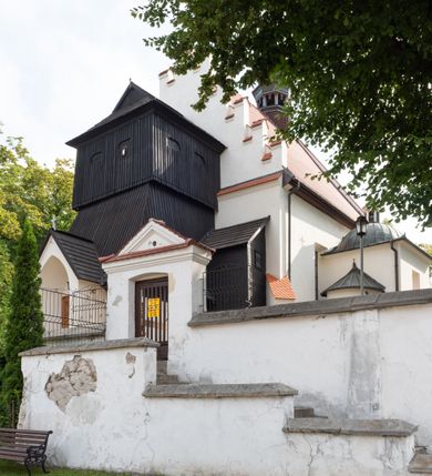 Zdjęcie nr 16: Kościół jest usytuowany w centrum wsi Rudawa, na północ od głównej drogi z Zabierzowa do Chrzanowa. Teren wokół niego jest otoczony wysokim, kamiennym murem z nieregularnych ciosów kamienia, oszkarpowanym, tynkowanym, z wyjątkiem zewnętrznej części muru na zachód od południowej bramki. W murze znajdują się trzy wejścia, od wschodu, południa i zachodu. W części wschodniej muru znajduje się trójosiowa brama wjazdowa, zwieńczona łukiem wklęsło-wypukłym, z trzema przelotami: środkowym wyższym i szerszym, zamkniętym łukiem odcinkowym i bocznymi węższymi i niższymi, zamkniętymi łukiem półkolistym (północne zamurowane). Część środkowa jest flankowana zdwojonymi pilastrami, podtrzymującymi profilowane uskokowe belkowanie z przyczółkiem o profilowanym łuku falistym, zwieńczonym równoramiennym krzyżem. W przyczółku wnęka z figurą św. Floriana. Bramki od strony zachodniej i południowej prostokątne, z przejściem zakończonym płaskim łukiem odcinkowym, z profilowanym gzymsem, zwieńczonym trójkątnym przyczółkiem. Przejścia zamykane drewnianymi ażurowymi i pomalowanymi na ciemnobrązowo jednoskrzydłowymi drzwiami. Poprzez bramkę od zachodu zejście kamiennymi schodami poprowadzonymi wzdłuż muru na dziedziniec plebański, usytuowany poniżej terenu kościelnego. 
W północno-wschodnim narożniku muru niewielka murowana i tynkowana kostnica na planie kwadratu, nakryta dachem namiotowym, łamanym, zakończonym ośmioboczną ślepą latarnią.

Po stronie południowej, poniżej placu kościelnego, do muru przylega murowana, tynkowana, prostokątna i dwukondygnacyjna „zegarowa” wieża bramna nakryta namiotowym dachem z wysoką drewnianą ośmioboczną latarnią o cebulastym hełmie. W wieży znajduje się przejazd wiodący na dziedziniec plebański, z sienią otwartą na przestrzał w dolnej kondygnacji i z lamusem dostępnym od strony placu kościelnego w górnej. 

W południowej części muru, w pobliżu południowo-wschodniego narożnika placu kościelnego, nadbudowana kamienna dzwonnica parawanowa z zawieszonymi czterema dzwonami.  

We wschodniej części placu kościelnego pomiędzy bramką wschodnią a kostnicą znajduje się kamienna ambona, o ośmiobocznej podstawie przechodzącej w szerszy, również ośmioboczny korpus, zakończony kamiennym parapetem, z kamiennymi schodami prowadzącymi na ambonę od strony wschodniej. 

Kościół jest orientowany, prawie w całości zbudowany z cegły, otynkowany z wyjątkiem prezbiterium. Wnętrze kościoła tworzy niewielkie, prostokątne, jednoprzęsłowe prezbiterium zakończone prostą ścianą i nakryte pozornym sklepieniem krzyżowo-żebrowym. Nawa jest szersza, prawie kwadratowa, nakryta drewnianym stropem. Prezbiterium z nawą są połączone szeroką, ostrołukową arkadą w ścianie tęczowej. Od północy do prezbiterium przylega założona na planie prostokąta dwuprzęsłowa zakrystia, nakryta sklepieniem krzyżowym. Wejście do zakrystii zaznaczone gotyckim, kamiennym, sfazowanym portalem zamkniętym łukiem ostrym. Od zachodu do zakrystii przylega niewielkie pomieszczenie gospodarcze, do którego z zakrystii prowadzą ostrołukowe drzwi. Zakrystia oświetlona ostrołukowym oknem w ścianie wschodniej, wypełnionym witrażem z tafelek w kształcie sześciokąta foremnego, ze szkła surowego, tzw. katedralnego. 

Od południa do nawy przylega kaplica o formach renesansowych, dwukondygnacyjna, założona na planie kwadratu. W dolnej kondygnacji sklepiona krzyżowo-żebrowo kruchta otwarta do nawy szeroką, zamkniętą półkoliście arkadą.

Ponad kruchtą kaplica św. Kazimierza, nakryta wspartą na pendentywach kopułą z latarnią. Z kruchty do kaplicy prowadzą kręte kamienne schody umieszczone od zachodu w półkolistej wieżyczce. Prostokątne wejście z krypty na klatkę schodową ujęte kamiennym profilowanym portalem. Kaplica otwarta do nawy szeroką, zamkniętą półkoliście arkadą, o kształcie i wymiarach analogicznych do arkady znajdującej się poniżej. Kaplicę, prócz latarni, oświetla prostokątne okno w ścianie południowej, wypełnione witrażem z tafelek w kształcie gomółek, ze szkła surowego, tzw. katedralnego. Na zachodniej ścianie nawy chór muzyczny, dostępny klatką schodową ukrytą w zewnętrznym aneksie przylegającym do zachodniej elewacji nawy i południowej elewacji wieży-dzwonnicy. 

Nawę i prezbiterium oświetlają umieszczone w południowych ścianach prostokątne, rozglifione okna: jedno w prezbiterium, dwa w nawie. Wszystkie wypełnione witrażami z tafelek w kształcie gomółek, ze szkła surowego, tzw. katedralnego. 

Do kościoła prowadzą dwa wejścia: poprzez arkadę z kruchty południowej oraz szerokie wejście główne prostokątne, zamknięte łukiem odcinkowym, prowadzące do kościoła z obszernej kruchty od strony zachodniej, znajdującej się w murowanym przyziemiu wieży - dzwonnicy. Kruchta, założona na planie kwadratu i nakryta murowanym stropem, doświetlona jest dwoma prostokątnymi oknami umieszczonymi naprzeciw siebie w ścianach północnej i południowej.
 
W zewnętrznej elewacji kościoła widoczny niewysoki kamienny cokół wykonany z nieregularnych ciosów kamienia. Prezbiterium, niższe od nawy, murowane z cegły w układzie wedyjskim, z domieszką układu polskiego. Wschodnie naroża prezbiterium zaakcentowane płaskimi lizenami. We wschodniej ścianie widoczny zarys zamurowanego wydłużonego okna zamkniętego lekko zaostrzonym łukiem, w trójkątnym szczycie znajduje się niewielkie wąskie okienko zakończone łukiem półkolistym. Południowa ściana prezbiterium ozdobiona fryzem z cegieł. Do ściany północnej prezbiterium przylega zakrystia, oszkarpowana, nakryta dachem pulpitowym, z dobudowanym od niej niewielkim aneksem, nakrytym takim samym zadaszeniem. Do wschodniej ściany prezbiterium przylega ogrójec nakryty dachem namiotowym z cebulastym zwieńczeniem, wspartym na sześciu smukłych, profilowanych drewnianych słupach z mieczami, pomiędzy którymi od północy i południa ażurowa drewniana balustrada. 

Nawa oszkarpowana w narożnikach. Elewacje bez podziałów architektonicznych. Od strony południowej do nawy dobudowana dwukondygnacyjna kaplica nakryta kopułą z latarnią, podzielona na dwie kondygnacje. W dolnej kondygnacji od południa wejście do kruchty zaznaczone kamiennym portalem o sfazowanych węgarach i lekko zaostrzonym łuku. Wejście zamykają drewniane dwuskrzydłowe drzwi ozdobione kratownicą z żelaznych listew. Od zachodu do kaplicy przylega półokrągła wieżyczka nakryta daszkiem stożkowym. 

Do zachodniej fasady kościoła dostawiona niska, założona na planie kwadratu trójkondygnacyjna wieża-dzwonnica: w dolnej części murowana, w narożach wzmocniona kamiennymi szkarpami, w górnej drewniana konstrukcji słupowo-ramowej z nadwieszoną izbicą i nakryta dachem półszczytowym. W dolnej, murowanej kondygnacji, na osi kościoła, prostokątne wejście do kruchty zaakcentowane przedsionkiem w kształcie ostrołukowej arkady i czterostopniowymi schodami. Przedsionek nakryty dachem dwuspadowym. Do zachodniej elewacji nawy i południowej elewacji dzwonnicy przylega niewielki, wysoki drewniany aneks, nakryty dachem pulpitowym, mieszczący klatkę schodową prowadzącą na górną kondygnację dzwonnicy i na chór muzyczny w nawie kościoła. Prostokątne wejście w południowej ścianie aneksu, do którego prowadzą pięciostopniowe proste schody. Ponad nimi, na wysokości drugiej kondygnacji dzwonnicy, niewielkie kwadratowe okno. 

Prezbiterium i nawa przykryte stromymi dachami dwuspadowymi, zamkniętymi od wschodu i zachodu szczytami sterczynowymi. Wieżyczka na sygnaturkę ośmioboczna, w dolnej części barokowa, w górnej części nowsza.