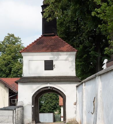 Zdjęcie nr 19: Kościół jest usytuowany w centrum wsi Rudawa, na północ od głównej drogi z Zabierzowa do Chrzanowa. Teren wokół niego jest otoczony wysokim, kamiennym murem z nieregularnych ciosów kamienia, oszkarpowanym, tynkowanym, z wyjątkiem zewnętrznej części muru na zachód od południowej bramki. W murze znajdują się trzy wejścia, od wschodu, południa i zachodu. W części wschodniej muru znajduje się trójosiowa brama wjazdowa, zwieńczona łukiem wklęsło-wypukłym, z trzema przelotami: środkowym wyższym i szerszym, zamkniętym łukiem odcinkowym i bocznymi węższymi i niższymi, zamkniętymi łukiem półkolistym (północne zamurowane). Część środkowa jest flankowana zdwojonymi pilastrami, podtrzymującymi profilowane uskokowe belkowanie z przyczółkiem o profilowanym łuku falistym, zwieńczonym równoramiennym krzyżem. W przyczółku wnęka z figurą św. Floriana. Bramki od strony zachodniej i południowej prostokątne, z przejściem zakończonym płaskim łukiem odcinkowym, z profilowanym gzymsem, zwieńczonym trójkątnym przyczółkiem. Przejścia zamykane drewnianymi ażurowymi i pomalowanymi na ciemnobrązowo jednoskrzydłowymi drzwiami. Poprzez bramkę od zachodu zejście kamiennymi schodami poprowadzonymi wzdłuż muru na dziedziniec plebański, usytuowany poniżej terenu kościelnego. 
W północno-wschodnim narożniku muru niewielka murowana i tynkowana kostnica na planie kwadratu, nakryta dachem namiotowym, łamanym, zakończonym ośmioboczną ślepą latarnią.

Po stronie południowej, poniżej placu kościelnego, do muru przylega murowana, tynkowana, prostokątna i dwukondygnacyjna „zegarowa” wieża bramna nakryta namiotowym dachem z wysoką drewnianą ośmioboczną latarnią o cebulastym hełmie. W wieży znajduje się przejazd wiodący na dziedziniec plebański, z sienią otwartą na przestrzał w dolnej kondygnacji i z lamusem dostępnym od strony placu kościelnego w górnej. 

W południowej części muru, w pobliżu południowo-wschodniego narożnika placu kościelnego, nadbudowana kamienna dzwonnica parawanowa z zawieszonymi czterema dzwonami.  

We wschodniej części placu kościelnego pomiędzy bramką wschodnią a kostnicą znajduje się kamienna ambona, o ośmiobocznej podstawie przechodzącej w szerszy, również ośmioboczny korpus, zakończony kamiennym parapetem, z kamiennymi schodami prowadzącymi na ambonę od strony wschodniej. 

Kościół jest orientowany, prawie w całości zbudowany z cegły, otynkowany z wyjątkiem prezbiterium. Wnętrze kościoła tworzy niewielkie, prostokątne, jednoprzęsłowe prezbiterium zakończone prostą ścianą i nakryte pozornym sklepieniem krzyżowo-żebrowym. Nawa jest szersza, prawie kwadratowa, nakryta drewnianym stropem. Prezbiterium z nawą są połączone szeroką, ostrołukową arkadą w ścianie tęczowej. Od północy do prezbiterium przylega założona na planie prostokąta dwuprzęsłowa zakrystia, nakryta sklepieniem krzyżowym. Wejście do zakrystii zaznaczone gotyckim, kamiennym, sfazowanym portalem zamkniętym łukiem ostrym. Od zachodu do zakrystii przylega niewielkie pomieszczenie gospodarcze, do którego z zakrystii prowadzą ostrołukowe drzwi. Zakrystia oświetlona ostrołukowym oknem w ścianie wschodniej, wypełnionym witrażem z tafelek w kształcie sześciokąta foremnego, ze szkła surowego, tzw. katedralnego. 

Od południa do nawy przylega kaplica o formach renesansowych, dwukondygnacyjna, założona na planie kwadratu. W dolnej kondygnacji sklepiona krzyżowo-żebrowo kruchta otwarta do nawy szeroką, zamkniętą półkoliście arkadą.

Ponad kruchtą kaplica św. Kazimierza, nakryta wspartą na pendentywach kopułą z latarnią. Z kruchty do kaplicy prowadzą kręte kamienne schody umieszczone od zachodu w półkolistej wieżyczce. Prostokątne wejście z krypty na klatkę schodową ujęte kamiennym profilowanym portalem. Kaplica otwarta do nawy szeroką, zamkniętą półkoliście arkadą, o kształcie i wymiarach analogicznych do arkady znajdującej się poniżej. Kaplicę, prócz latarni, oświetla prostokątne okno w ścianie południowej, wypełnione witrażem z tafelek w kształcie gomółek, ze szkła surowego, tzw. katedralnego. Na zachodniej ścianie nawy chór muzyczny, dostępny klatką schodową ukrytą w zewnętrznym aneksie przylegającym do zachodniej elewacji nawy i południowej elewacji wieży-dzwonnicy. 

Nawę i prezbiterium oświetlają umieszczone w południowych ścianach prostokątne, rozglifione okna: jedno w prezbiterium, dwa w nawie. Wszystkie wypełnione witrażami z tafelek w kształcie gomółek, ze szkła surowego, tzw. katedralnego. 

Do kościoła prowadzą dwa wejścia: poprzez arkadę z kruchty południowej oraz szerokie wejście główne prostokątne, zamknięte łukiem odcinkowym, prowadzące do kościoła z obszernej kruchty od strony zachodniej, znajdującej się w murowanym przyziemiu wieży - dzwonnicy. Kruchta, założona na planie kwadratu i nakryta murowanym stropem, doświetlona jest dwoma prostokątnymi oknami umieszczonymi naprzeciw siebie w ścianach północnej i południowej.
 
W zewnętrznej elewacji kościoła widoczny niewysoki kamienny cokół wykonany z nieregularnych ciosów kamienia. Prezbiterium, niższe od nawy, murowane z cegły w układzie wedyjskim, z domieszką układu polskiego. Wschodnie naroża prezbiterium zaakcentowane płaskimi lizenami. We wschodniej ścianie widoczny zarys zamurowanego wydłużonego okna zamkniętego lekko zaostrzonym łukiem, w trójkątnym szczycie znajduje się niewielkie wąskie okienko zakończone łukiem półkolistym. Południowa ściana prezbiterium ozdobiona fryzem z cegieł. Do ściany północnej prezbiterium przylega zakrystia, oszkarpowana, nakryta dachem pulpitowym, z dobudowanym od niej niewielkim aneksem, nakrytym takim samym zadaszeniem. Do wschodniej ściany prezbiterium przylega ogrójec nakryty dachem namiotowym z cebulastym zwieńczeniem, wspartym na sześciu smukłych, profilowanych drewnianych słupach z mieczami, pomiędzy którymi od północy i południa ażurowa drewniana balustrada. 

Nawa oszkarpowana w narożnikach. Elewacje bez podziałów architektonicznych. Od strony południowej do nawy dobudowana dwukondygnacyjna kaplica nakryta kopułą z latarnią, podzielona na dwie kondygnacje. W dolnej kondygnacji od południa wejście do kruchty zaznaczone kamiennym portalem o sfazowanych węgarach i lekko zaostrzonym łuku. Wejście zamykają drewniane dwuskrzydłowe drzwi ozdobione kratownicą z żelaznych listew. Od zachodu do kaplicy przylega półokrągła wieżyczka nakryta daszkiem stożkowym. 

Do zachodniej fasady kościoła dostawiona niska, założona na planie kwadratu trójkondygnacyjna wieża-dzwonnica: w dolnej części murowana, w narożach wzmocniona kamiennymi szkarpami, w górnej drewniana konstrukcji słupowo-ramowej z nadwieszoną izbicą i nakryta dachem półszczytowym. W dolnej, murowanej kondygnacji, na osi kościoła, prostokątne wejście do kruchty zaakcentowane przedsionkiem w kształcie ostrołukowej arkady i czterostopniowymi schodami. Przedsionek nakryty dachem dwuspadowym. Do zachodniej elewacji nawy i południowej elewacji dzwonnicy przylega niewielki, wysoki drewniany aneks, nakryty dachem pulpitowym, mieszczący klatkę schodową prowadzącą na górną kondygnację dzwonnicy i na chór muzyczny w nawie kościoła. Prostokątne wejście w południowej ścianie aneksu, do którego prowadzą pięciostopniowe proste schody. Ponad nimi, na wysokości drugiej kondygnacji dzwonnicy, niewielkie kwadratowe okno. 

Prezbiterium i nawa przykryte stromymi dachami dwuspadowymi, zamkniętymi od wschodu i zachodu szczytami sterczynowymi. Wieżyczka na sygnaturkę ośmioboczna, w dolnej części barokowa, w górnej części nowsza.