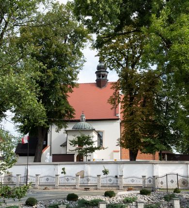 Zdjęcie nr 17: Kościół jest usytuowany w centrum wsi Rudawa, na północ od głównej drogi z Zabierzowa do Chrzanowa. Teren wokół niego jest otoczony wysokim, kamiennym murem z nieregularnych ciosów kamienia, oszkarpowanym, tynkowanym, z wyjątkiem zewnętrznej części muru na zachód od południowej bramki. W murze znajdują się trzy wejścia, od wschodu, południa i zachodu. W części wschodniej muru znajduje się trójosiowa brama wjazdowa, zwieńczona łukiem wklęsło-wypukłym, z trzema przelotami: środkowym wyższym i szerszym, zamkniętym łukiem odcinkowym i bocznymi węższymi i niższymi, zamkniętymi łukiem półkolistym (północne zamurowane). Część środkowa jest flankowana zdwojonymi pilastrami, podtrzymującymi profilowane uskokowe belkowanie z przyczółkiem o profilowanym łuku falistym, zwieńczonym równoramiennym krzyżem. W przyczółku wnęka z figurą św. Floriana. Bramki od strony zachodniej i południowej prostokątne, z przejściem zakończonym płaskim łukiem odcinkowym, z profilowanym gzymsem, zwieńczonym trójkątnym przyczółkiem. Przejścia zamykane drewnianymi ażurowymi i pomalowanymi na ciemnobrązowo jednoskrzydłowymi drzwiami. Poprzez bramkę od zachodu zejście kamiennymi schodami poprowadzonymi wzdłuż muru na dziedziniec plebański, usytuowany poniżej terenu kościelnego. 
W północno-wschodnim narożniku muru niewielka murowana i tynkowana kostnica na planie kwadratu, nakryta dachem namiotowym, łamanym, zakończonym ośmioboczną ślepą latarnią.

Po stronie południowej, poniżej placu kościelnego, do muru przylega murowana, tynkowana, prostokątna i dwukondygnacyjna „zegarowa” wieża bramna nakryta namiotowym dachem z wysoką drewnianą ośmioboczną latarnią o cebulastym hełmie. W wieży znajduje się przejazd wiodący na dziedziniec plebański, z sienią otwartą na przestrzał w dolnej kondygnacji i z lamusem dostępnym od strony placu kościelnego w górnej. 

W południowej części muru, w pobliżu południowo-wschodniego narożnika placu kościelnego, nadbudowana kamienna dzwonnica parawanowa z zawieszonymi czterema dzwonami.  

We wschodniej części placu kościelnego pomiędzy bramką wschodnią a kostnicą znajduje się kamienna ambona, o ośmiobocznej podstawie przechodzącej w szerszy, również ośmioboczny korpus, zakończony kamiennym parapetem, z kamiennymi schodami prowadzącymi na ambonę od strony wschodniej. 

Kościół jest orientowany, prawie w całości zbudowany z cegły, otynkowany z wyjątkiem prezbiterium. Wnętrze kościoła tworzy niewielkie, prostokątne, jednoprzęsłowe prezbiterium zakończone prostą ścianą i nakryte pozornym sklepieniem krzyżowo-żebrowym. Nawa jest szersza, prawie kwadratowa, nakryta drewnianym stropem. Prezbiterium z nawą są połączone szeroką, ostrołukową arkadą w ścianie tęczowej. Od północy do prezbiterium przylega założona na planie prostokąta dwuprzęsłowa zakrystia, nakryta sklepieniem krzyżowym. Wejście do zakrystii zaznaczone gotyckim, kamiennym, sfazowanym portalem zamkniętym łukiem ostrym. Od zachodu do zakrystii przylega niewielkie pomieszczenie gospodarcze, do którego z zakrystii prowadzą ostrołukowe drzwi. Zakrystia oświetlona ostrołukowym oknem w ścianie wschodniej, wypełnionym witrażem z tafelek w kształcie sześciokąta foremnego, ze szkła surowego, tzw. katedralnego. 

Od południa do nawy przylega kaplica o formach renesansowych, dwukondygnacyjna, założona na planie kwadratu. W dolnej kondygnacji sklepiona krzyżowo-żebrowo kruchta otwarta do nawy szeroką, zamkniętą półkoliście arkadą.

Ponad kruchtą kaplica św. Kazimierza, nakryta wspartą na pendentywach kopułą z latarnią. Z kruchty do kaplicy prowadzą kręte kamienne schody umieszczone od zachodu w półkolistej wieżyczce. Prostokątne wejście z krypty na klatkę schodową ujęte kamiennym profilowanym portalem. Kaplica otwarta do nawy szeroką, zamkniętą półkoliście arkadą, o kształcie i wymiarach analogicznych do arkady znajdującej się poniżej. Kaplicę, prócz latarni, oświetla prostokątne okno w ścianie południowej, wypełnione witrażem z tafelek w kształcie gomółek, ze szkła surowego, tzw. katedralnego. Na zachodniej ścianie nawy chór muzyczny, dostępny klatką schodową ukrytą w zewnętrznym aneksie przylegającym do zachodniej elewacji nawy i południowej elewacji wieży-dzwonnicy. 

Nawę i prezbiterium oświetlają umieszczone w południowych ścianach prostokątne, rozglifione okna: jedno w prezbiterium, dwa w nawie. Wszystkie wypełnione witrażami z tafelek w kształcie gomółek, ze szkła surowego, tzw. katedralnego. 

Do kościoła prowadzą dwa wejścia: poprzez arkadę z kruchty południowej oraz szerokie wejście główne prostokątne, zamknięte łukiem odcinkowym, prowadzące do kościoła z obszernej kruchty od strony zachodniej, znajdującej się w murowanym przyziemiu wieży - dzwonnicy. Kruchta, założona na planie kwadratu i nakryta murowanym stropem, doświetlona jest dwoma prostokątnymi oknami umieszczonymi naprzeciw siebie w ścianach północnej i południowej.
 
W zewnętrznej elewacji kościoła widoczny niewysoki kamienny cokół wykonany z nieregularnych ciosów kamienia. Prezbiterium, niższe od nawy, murowane z cegły w układzie wedyjskim, z domieszką układu polskiego. Wschodnie naroża prezbiterium zaakcentowane płaskimi lizenami. We wschodniej ścianie widoczny zarys zamurowanego wydłużonego okna zamkniętego lekko zaostrzonym łukiem, w trójkątnym szczycie znajduje się niewielkie wąskie okienko zakończone łukiem półkolistym. Południowa ściana prezbiterium ozdobiona fryzem z cegieł. Do ściany północnej prezbiterium przylega zakrystia, oszkarpowana, nakryta dachem pulpitowym, z dobudowanym od niej niewielkim aneksem, nakrytym takim samym zadaszeniem. Do wschodniej ściany prezbiterium przylega ogrójec nakryty dachem namiotowym z cebulastym zwieńczeniem, wspartym na sześciu smukłych, profilowanych drewnianych słupach z mieczami, pomiędzy którymi od północy i południa ażurowa drewniana balustrada. 

Nawa oszkarpowana w narożnikach. Elewacje bez podziałów architektonicznych. Od strony południowej do nawy dobudowana dwukondygnacyjna kaplica nakryta kopułą z latarnią, podzielona na dwie kondygnacje. W dolnej kondygnacji od południa wejście do kruchty zaznaczone kamiennym portalem o sfazowanych węgarach i lekko zaostrzonym łuku. Wejście zamykają drewniane dwuskrzydłowe drzwi ozdobione kratownicą z żelaznych listew. Od zachodu do kaplicy przylega półokrągła wieżyczka nakryta daszkiem stożkowym. 

Do zachodniej fasady kościoła dostawiona niska, założona na planie kwadratu trójkondygnacyjna wieża-dzwonnica: w dolnej części murowana, w narożach wzmocniona kamiennymi szkarpami, w górnej drewniana konstrukcji słupowo-ramowej z nadwieszoną izbicą i nakryta dachem półszczytowym. W dolnej, murowanej kondygnacji, na osi kościoła, prostokątne wejście do kruchty zaakcentowane przedsionkiem w kształcie ostrołukowej arkady i czterostopniowymi schodami. Przedsionek nakryty dachem dwuspadowym. Do zachodniej elewacji nawy i południowej elewacji dzwonnicy przylega niewielki, wysoki drewniany aneks, nakryty dachem pulpitowym, mieszczący klatkę schodową prowadzącą na górną kondygnację dzwonnicy i na chór muzyczny w nawie kościoła. Prostokątne wejście w południowej ścianie aneksu, do którego prowadzą pięciostopniowe proste schody. Ponad nimi, na wysokości drugiej kondygnacji dzwonnicy, niewielkie kwadratowe okno. 

Prezbiterium i nawa przykryte stromymi dachami dwuspadowymi, zamkniętymi od wschodu i zachodu szczytami sterczynowymi. Wieżyczka na sygnaturkę ośmioboczna, w dolnej części barokowa, w górnej części nowsza.
