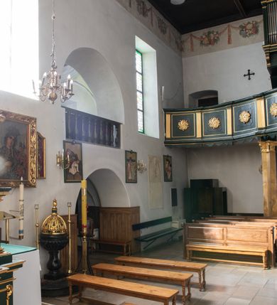 Zdjęcie nr 39: Kościół jest usytuowany w centrum wsi Rudawa, na północ od głównej drogi z Zabierzowa do Chrzanowa. Teren wokół niego jest otoczony wysokim, kamiennym murem z nieregularnych ciosów kamienia, oszkarpowanym, tynkowanym, z wyjątkiem zewnętrznej części muru na zachód od południowej bramki. W murze znajdują się trzy wejścia, od wschodu, południa i zachodu. W części wschodniej muru znajduje się trójosiowa brama wjazdowa, zwieńczona łukiem wklęsło-wypukłym, z trzema przelotami: środkowym wyższym i szerszym, zamkniętym łukiem odcinkowym i bocznymi węższymi i niższymi, zamkniętymi łukiem półkolistym (północne zamurowane). Część środkowa jest flankowana zdwojonymi pilastrami, podtrzymującymi profilowane uskokowe belkowanie z przyczółkiem o profilowanym łuku falistym, zwieńczonym równoramiennym krzyżem. W przyczółku wnęka z figurą św. Floriana. Bramki od strony zachodniej i południowej prostokątne, z przejściem zakończonym płaskim łukiem odcinkowym, z profilowanym gzymsem, zwieńczonym trójkątnym przyczółkiem. Przejścia zamykane drewnianymi ażurowymi i pomalowanymi na ciemnobrązowo jednoskrzydłowymi drzwiami. Poprzez bramkę od zachodu zejście kamiennymi schodami poprowadzonymi wzdłuż muru na dziedziniec plebański, usytuowany poniżej terenu kościelnego. 
W północno-wschodnim narożniku muru niewielka murowana i tynkowana kostnica na planie kwadratu, nakryta dachem namiotowym, łamanym, zakończonym ośmioboczną ślepą latarnią.

Po stronie południowej, poniżej placu kościelnego, do muru przylega murowana, tynkowana, prostokątna i dwukondygnacyjna „zegarowa” wieża bramna nakryta namiotowym dachem z wysoką drewnianą ośmioboczną latarnią o cebulastym hełmie. W wieży znajduje się przejazd wiodący na dziedziniec plebański, z sienią otwartą na przestrzał w dolnej kondygnacji i z lamusem dostępnym od strony placu kościelnego w górnej. 

W południowej części muru, w pobliżu południowo-wschodniego narożnika placu kościelnego, nadbudowana kamienna dzwonnica parawanowa z zawieszonymi czterema dzwonami.  

We wschodniej części placu kościelnego pomiędzy bramką wschodnią a kostnicą znajduje się kamienna ambona, o ośmiobocznej podstawie przechodzącej w szerszy, również ośmioboczny korpus, zakończony kamiennym parapetem, z kamiennymi schodami prowadzącymi na ambonę od strony wschodniej. 

Kościół jest orientowany, prawie w całości zbudowany z cegły, otynkowany z wyjątkiem prezbiterium. Wnętrze kościoła tworzy niewielkie, prostokątne, jednoprzęsłowe prezbiterium zakończone prostą ścianą i nakryte pozornym sklepieniem krzyżowo-żebrowym. Nawa jest szersza, prawie kwadratowa, nakryta drewnianym stropem. Prezbiterium z nawą są połączone szeroką, ostrołukową arkadą w ścianie tęczowej. Od północy do prezbiterium przylega założona na planie prostokąta dwuprzęsłowa zakrystia, nakryta sklepieniem krzyżowym. Wejście do zakrystii zaznaczone gotyckim, kamiennym, sfazowanym portalem zamkniętym łukiem ostrym. Od zachodu do zakrystii przylega niewielkie pomieszczenie gospodarcze, do którego z zakrystii prowadzą ostrołukowe drzwi. Zakrystia oświetlona ostrołukowym oknem w ścianie wschodniej, wypełnionym witrażem z tafelek w kształcie sześciokąta foremnego, ze szkła surowego, tzw. katedralnego. 

Od południa do nawy przylega kaplica o formach renesansowych, dwukondygnacyjna, założona na planie kwadratu. W dolnej kondygnacji sklepiona krzyżowo-żebrowo kruchta otwarta do nawy szeroką, zamkniętą półkoliście arkadą.

Ponad kruchtą kaplica św. Kazimierza, nakryta wspartą na pendentywach kopułą z latarnią. Z kruchty do kaplicy prowadzą kręte kamienne schody umieszczone od zachodu w półkolistej wieżyczce. Prostokątne wejście z krypty na klatkę schodową ujęte kamiennym profilowanym portalem. Kaplica otwarta do nawy szeroką, zamkniętą półkoliście arkadą, o kształcie i wymiarach analogicznych do arkady znajdującej się poniżej. Kaplicę, prócz latarni, oświetla prostokątne okno w ścianie południowej, wypełnione witrażem z tafelek w kształcie gomółek, ze szkła surowego, tzw. katedralnego. Na zachodniej ścianie nawy chór muzyczny, dostępny klatką schodową ukrytą w zewnętrznym aneksie przylegającym do zachodniej elewacji nawy i południowej elewacji wieży-dzwonnicy. 

Nawę i prezbiterium oświetlają umieszczone w południowych ścianach prostokątne, rozglifione okna: jedno w prezbiterium, dwa w nawie. Wszystkie wypełnione witrażami z tafelek w kształcie gomółek, ze szkła surowego, tzw. katedralnego. 

Do kościoła prowadzą dwa wejścia: poprzez arkadę z kruchty południowej oraz szerokie wejście główne prostokątne, zamknięte łukiem odcinkowym, prowadzące do kościoła z obszernej kruchty od strony zachodniej, znajdującej się w murowanym przyziemiu wieży - dzwonnicy. Kruchta, założona na planie kwadratu i nakryta murowanym stropem, doświetlona jest dwoma prostokątnymi oknami umieszczonymi naprzeciw siebie w ścianach północnej i południowej.
 
W zewnętrznej elewacji kościoła widoczny niewysoki kamienny cokół wykonany z nieregularnych ciosów kamienia. Prezbiterium, niższe od nawy, murowane z cegły w układzie wedyjskim, z domieszką układu polskiego. Wschodnie naroża prezbiterium zaakcentowane płaskimi lizenami. We wschodniej ścianie widoczny zarys zamurowanego wydłużonego okna zamkniętego lekko zaostrzonym łukiem, w trójkątnym szczycie znajduje się niewielkie wąskie okienko zakończone łukiem półkolistym. Południowa ściana prezbiterium ozdobiona fryzem z cegieł. Do ściany północnej prezbiterium przylega zakrystia, oszkarpowana, nakryta dachem pulpitowym, z dobudowanym od niej niewielkim aneksem, nakrytym takim samym zadaszeniem. Do wschodniej ściany prezbiterium przylega ogrójec nakryty dachem namiotowym z cebulastym zwieńczeniem, wspartym na sześciu smukłych, profilowanych drewnianych słupach z mieczami, pomiędzy którymi od północy i południa ażurowa drewniana balustrada. 

Nawa oszkarpowana w narożnikach. Elewacje bez podziałów architektonicznych. Od strony południowej do nawy dobudowana dwukondygnacyjna kaplica nakryta kopułą z latarnią, podzielona na dwie kondygnacje. W dolnej kondygnacji od południa wejście do kruchty zaznaczone kamiennym portalem o sfazowanych węgarach i lekko zaostrzonym łuku. Wejście zamykają drewniane dwuskrzydłowe drzwi ozdobione kratownicą z żelaznych listew. Od zachodu do kaplicy przylega półokrągła wieżyczka nakryta daszkiem stożkowym. 

Do zachodniej fasady kościoła dostawiona niska, założona na planie kwadratu trójkondygnacyjna wieża-dzwonnica: w dolnej części murowana, w narożach wzmocniona kamiennymi szkarpami, w górnej drewniana konstrukcji słupowo-ramowej z nadwieszoną izbicą i nakryta dachem półszczytowym. W dolnej, murowanej kondygnacji, na osi kościoła, prostokątne wejście do kruchty zaakcentowane przedsionkiem w kształcie ostrołukowej arkady i czterostopniowymi schodami. Przedsionek nakryty dachem dwuspadowym. Do zachodniej elewacji nawy i południowej elewacji dzwonnicy przylega niewielki, wysoki drewniany aneks, nakryty dachem pulpitowym, mieszczący klatkę schodową prowadzącą na górną kondygnację dzwonnicy i na chór muzyczny w nawie kościoła. Prostokątne wejście w południowej ścianie aneksu, do którego prowadzą pięciostopniowe proste schody. Ponad nimi, na wysokości drugiej kondygnacji dzwonnicy, niewielkie kwadratowe okno. 

Prezbiterium i nawa przykryte stromymi dachami dwuspadowymi, zamkniętymi od wschodu i zachodu szczytami sterczynowymi. Wieżyczka na sygnaturkę ośmioboczna, w dolnej części barokowa, w górnej części nowsza.