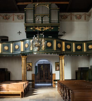 Zdjęcie nr 40: Kościół jest usytuowany w centrum wsi Rudawa, na północ od głównej drogi z Zabierzowa do Chrzanowa. Teren wokół niego jest otoczony wysokim, kamiennym murem z nieregularnych ciosów kamienia, oszkarpowanym, tynkowanym, z wyjątkiem zewnętrznej części muru na zachód od południowej bramki. W murze znajdują się trzy wejścia, od wschodu, południa i zachodu. W części wschodniej muru znajduje się trójosiowa brama wjazdowa, zwieńczona łukiem wklęsło-wypukłym, z trzema przelotami: środkowym wyższym i szerszym, zamkniętym łukiem odcinkowym i bocznymi węższymi i niższymi, zamkniętymi łukiem półkolistym (północne zamurowane). Część środkowa jest flankowana zdwojonymi pilastrami, podtrzymującymi profilowane uskokowe belkowanie z przyczółkiem o profilowanym łuku falistym, zwieńczonym równoramiennym krzyżem. W przyczółku wnęka z figurą św. Floriana. Bramki od strony zachodniej i południowej prostokątne, z przejściem zakończonym płaskim łukiem odcinkowym, z profilowanym gzymsem, zwieńczonym trójkątnym przyczółkiem. Przejścia zamykane drewnianymi ażurowymi i pomalowanymi na ciemnobrązowo jednoskrzydłowymi drzwiami. Poprzez bramkę od zachodu zejście kamiennymi schodami poprowadzonymi wzdłuż muru na dziedziniec plebański, usytuowany poniżej terenu kościelnego. 
W północno-wschodnim narożniku muru niewielka murowana i tynkowana kostnica na planie kwadratu, nakryta dachem namiotowym, łamanym, zakończonym ośmioboczną ślepą latarnią.

Po stronie południowej, poniżej placu kościelnego, do muru przylega murowana, tynkowana, prostokątna i dwukondygnacyjna „zegarowa” wieża bramna nakryta namiotowym dachem z wysoką drewnianą ośmioboczną latarnią o cebulastym hełmie. W wieży znajduje się przejazd wiodący na dziedziniec plebański, z sienią otwartą na przestrzał w dolnej kondygnacji i z lamusem dostępnym od strony placu kościelnego w górnej. 

W południowej części muru, w pobliżu południowo-wschodniego narożnika placu kościelnego, nadbudowana kamienna dzwonnica parawanowa z zawieszonymi czterema dzwonami.  

We wschodniej części placu kościelnego pomiędzy bramką wschodnią a kostnicą znajduje się kamienna ambona, o ośmiobocznej podstawie przechodzącej w szerszy, również ośmioboczny korpus, zakończony kamiennym parapetem, z kamiennymi schodami prowadzącymi na ambonę od strony wschodniej. 

Kościół jest orientowany, prawie w całości zbudowany z cegły, otynkowany z wyjątkiem prezbiterium. Wnętrze kościoła tworzy niewielkie, prostokątne, jednoprzęsłowe prezbiterium zakończone prostą ścianą i nakryte pozornym sklepieniem krzyżowo-żebrowym. Nawa jest szersza, prawie kwadratowa, nakryta drewnianym stropem. Prezbiterium z nawą są połączone szeroką, ostrołukową arkadą w ścianie tęczowej. Od północy do prezbiterium przylega założona na planie prostokąta dwuprzęsłowa zakrystia, nakryta sklepieniem krzyżowym. Wejście do zakrystii zaznaczone gotyckim, kamiennym, sfazowanym portalem zamkniętym łukiem ostrym. Od zachodu do zakrystii przylega niewielkie pomieszczenie gospodarcze, do którego z zakrystii prowadzą ostrołukowe drzwi. Zakrystia oświetlona ostrołukowym oknem w ścianie wschodniej, wypełnionym witrażem z tafelek w kształcie sześciokąta foremnego, ze szkła surowego, tzw. katedralnego. 

Od południa do nawy przylega kaplica o formach renesansowych, dwukondygnacyjna, założona na planie kwadratu. W dolnej kondygnacji sklepiona krzyżowo-żebrowo kruchta otwarta do nawy szeroką, zamkniętą półkoliście arkadą.

Ponad kruchtą kaplica św. Kazimierza, nakryta wspartą na pendentywach kopułą z latarnią. Z kruchty do kaplicy prowadzą kręte kamienne schody umieszczone od zachodu w półkolistej wieżyczce. Prostokątne wejście z krypty na klatkę schodową ujęte kamiennym profilowanym portalem. Kaplica otwarta do nawy szeroką, zamkniętą półkoliście arkadą, o kształcie i wymiarach analogicznych do arkady znajdującej się poniżej. Kaplicę, prócz latarni, oświetla prostokątne okno w ścianie południowej, wypełnione witrażem z tafelek w kształcie gomółek, ze szkła surowego, tzw. katedralnego. Na zachodniej ścianie nawy chór muzyczny, dostępny klatką schodową ukrytą w zewnętrznym aneksie przylegającym do zachodniej elewacji nawy i południowej elewacji wieży-dzwonnicy. 

Nawę i prezbiterium oświetlają umieszczone w południowych ścianach prostokątne, rozglifione okna: jedno w prezbiterium, dwa w nawie. Wszystkie wypełnione witrażami z tafelek w kształcie gomółek, ze szkła surowego, tzw. katedralnego. 

Do kościoła prowadzą dwa wejścia: poprzez arkadę z kruchty południowej oraz szerokie wejście główne prostokątne, zamknięte łukiem odcinkowym, prowadzące do kościoła z obszernej kruchty od strony zachodniej, znajdującej się w murowanym przyziemiu wieży - dzwonnicy. Kruchta, założona na planie kwadratu i nakryta murowanym stropem, doświetlona jest dwoma prostokątnymi oknami umieszczonymi naprzeciw siebie w ścianach północnej i południowej.
 
W zewnętrznej elewacji kościoła widoczny niewysoki kamienny cokół wykonany z nieregularnych ciosów kamienia. Prezbiterium, niższe od nawy, murowane z cegły w układzie wedyjskim, z domieszką układu polskiego. Wschodnie naroża prezbiterium zaakcentowane płaskimi lizenami. We wschodniej ścianie widoczny zarys zamurowanego wydłużonego okna zamkniętego lekko zaostrzonym łukiem, w trójkątnym szczycie znajduje się niewielkie wąskie okienko zakończone łukiem półkolistym. Południowa ściana prezbiterium ozdobiona fryzem z cegieł. Do ściany północnej prezbiterium przylega zakrystia, oszkarpowana, nakryta dachem pulpitowym, z dobudowanym od niej niewielkim aneksem, nakrytym takim samym zadaszeniem. Do wschodniej ściany prezbiterium przylega ogrójec nakryty dachem namiotowym z cebulastym zwieńczeniem, wspartym na sześciu smukłych, profilowanych drewnianych słupach z mieczami, pomiędzy którymi od północy i południa ażurowa drewniana balustrada. 

Nawa oszkarpowana w narożnikach. Elewacje bez podziałów architektonicznych. Od strony południowej do nawy dobudowana dwukondygnacyjna kaplica nakryta kopułą z latarnią, podzielona na dwie kondygnacje. W dolnej kondygnacji od południa wejście do kruchty zaznaczone kamiennym portalem o sfazowanych węgarach i lekko zaostrzonym łuku. Wejście zamykają drewniane dwuskrzydłowe drzwi ozdobione kratownicą z żelaznych listew. Od zachodu do kaplicy przylega półokrągła wieżyczka nakryta daszkiem stożkowym. 

Do zachodniej fasady kościoła dostawiona niska, założona na planie kwadratu trójkondygnacyjna wieża-dzwonnica: w dolnej części murowana, w narożach wzmocniona kamiennymi szkarpami, w górnej drewniana konstrukcji słupowo-ramowej z nadwieszoną izbicą i nakryta dachem półszczytowym. W dolnej, murowanej kondygnacji, na osi kościoła, prostokątne wejście do kruchty zaakcentowane przedsionkiem w kształcie ostrołukowej arkady i czterostopniowymi schodami. Przedsionek nakryty dachem dwuspadowym. Do zachodniej elewacji nawy i południowej elewacji dzwonnicy przylega niewielki, wysoki drewniany aneks, nakryty dachem pulpitowym, mieszczący klatkę schodową prowadzącą na górną kondygnację dzwonnicy i na chór muzyczny w nawie kościoła. Prostokątne wejście w południowej ścianie aneksu, do którego prowadzą pięciostopniowe proste schody. Ponad nimi, na wysokości drugiej kondygnacji dzwonnicy, niewielkie kwadratowe okno. 

Prezbiterium i nawa przykryte stromymi dachami dwuspadowymi, zamkniętymi od wschodu i zachodu szczytami sterczynowymi. Wieżyczka na sygnaturkę ośmioboczna, w dolnej części barokowa, w górnej części nowsza.