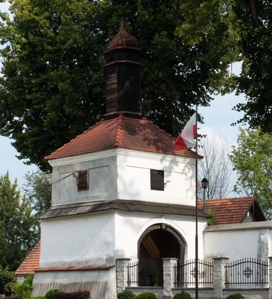 Zdjęcie nr 43: Kościół jest usytuowany w centrum wsi Rudawa, na północ od głównej drogi z Zabierzowa do Chrzanowa. Teren wokół niego jest otoczony wysokim, kamiennym murem z nieregularnych ciosów kamienia, oszkarpowanym, tynkowanym, z wyjątkiem zewnętrznej części muru na zachód od południowej bramki. W murze znajdują się trzy wejścia, od wschodu, południa i zachodu. W części wschodniej muru znajduje się trójosiowa brama wjazdowa, zwieńczona łukiem wklęsło-wypukłym, z trzema przelotami: środkowym wyższym i szerszym, zamkniętym łukiem odcinkowym i bocznymi węższymi i niższymi, zamkniętymi łukiem półkolistym (północne zamurowane). Część środkowa jest flankowana zdwojonymi pilastrami, podtrzymującymi profilowane uskokowe belkowanie z przyczółkiem o profilowanym łuku falistym, zwieńczonym równoramiennym krzyżem. W przyczółku wnęka z figurą św. Floriana. Bramki od strony zachodniej i południowej prostokątne, z przejściem zakończonym płaskim łukiem odcinkowym, z profilowanym gzymsem, zwieńczonym trójkątnym przyczółkiem. Przejścia zamykane drewnianymi ażurowymi i pomalowanymi na ciemnobrązowo jednoskrzydłowymi drzwiami. Poprzez bramkę od zachodu zejście kamiennymi schodami poprowadzonymi wzdłuż muru na dziedziniec plebański, usytuowany poniżej terenu kościelnego. 
W północno-wschodnim narożniku muru niewielka murowana i tynkowana kostnica na planie kwadratu, nakryta dachem namiotowym, łamanym, zakończonym ośmioboczną ślepą latarnią.

Po stronie południowej, poniżej placu kościelnego, do muru przylega murowana, tynkowana, prostokątna i dwukondygnacyjna „zegarowa” wieża bramna nakryta namiotowym dachem z wysoką drewnianą ośmioboczną latarnią o cebulastym hełmie. W wieży znajduje się przejazd wiodący na dziedziniec plebański, z sienią otwartą na przestrzał w dolnej kondygnacji i z lamusem dostępnym od strony placu kościelnego w górnej. 

W południowej części muru, w pobliżu południowo-wschodniego narożnika placu kościelnego, nadbudowana kamienna dzwonnica parawanowa z zawieszonymi czterema dzwonami.  

We wschodniej części placu kościelnego pomiędzy bramką wschodnią a kostnicą znajduje się kamienna ambona, o ośmiobocznej podstawie przechodzącej w szerszy, również ośmioboczny korpus, zakończony kamiennym parapetem, z kamiennymi schodami prowadzącymi na ambonę od strony wschodniej. 

Kościół jest orientowany, prawie w całości zbudowany z cegły, otynkowany z wyjątkiem prezbiterium. Wnętrze kościoła tworzy niewielkie, prostokątne, jednoprzęsłowe prezbiterium zakończone prostą ścianą i nakryte pozornym sklepieniem krzyżowo-żebrowym. Nawa jest szersza, prawie kwadratowa, nakryta drewnianym stropem. Prezbiterium z nawą są połączone szeroką, ostrołukową arkadą w ścianie tęczowej. Od północy do prezbiterium przylega założona na planie prostokąta dwuprzęsłowa zakrystia, nakryta sklepieniem krzyżowym. Wejście do zakrystii zaznaczone gotyckim, kamiennym, sfazowanym portalem zamkniętym łukiem ostrym. Od zachodu do zakrystii przylega niewielkie pomieszczenie gospodarcze, do którego z zakrystii prowadzą ostrołukowe drzwi. Zakrystia oświetlona ostrołukowym oknem w ścianie wschodniej, wypełnionym witrażem z tafelek w kształcie sześciokąta foremnego, ze szkła surowego, tzw. katedralnego. 

Od południa do nawy przylega kaplica o formach renesansowych, dwukondygnacyjna, założona na planie kwadratu. W dolnej kondygnacji sklepiona krzyżowo-żebrowo kruchta otwarta do nawy szeroką, zamkniętą półkoliście arkadą.

Ponad kruchtą kaplica św. Kazimierza, nakryta wspartą na pendentywach kopułą z latarnią. Z kruchty do kaplicy prowadzą kręte kamienne schody umieszczone od zachodu w półkolistej wieżyczce. Prostokątne wejście z krypty na klatkę schodową ujęte kamiennym profilowanym portalem. Kaplica otwarta do nawy szeroką, zamkniętą półkoliście arkadą, o kształcie i wymiarach analogicznych do arkady znajdującej się poniżej. Kaplicę, prócz latarni, oświetla prostokątne okno w ścianie południowej, wypełnione witrażem z tafelek w kształcie gomółek, ze szkła surowego, tzw. katedralnego. Na zachodniej ścianie nawy chór muzyczny, dostępny klatką schodową ukrytą w zewnętrznym aneksie przylegającym do zachodniej elewacji nawy i południowej elewacji wieży-dzwonnicy. 

Nawę i prezbiterium oświetlają umieszczone w południowych ścianach prostokątne, rozglifione okna: jedno w prezbiterium, dwa w nawie. Wszystkie wypełnione witrażami z tafelek w kształcie gomółek, ze szkła surowego, tzw. katedralnego. 

Do kościoła prowadzą dwa wejścia: poprzez arkadę z kruchty południowej oraz szerokie wejście główne prostokątne, zamknięte łukiem odcinkowym, prowadzące do kościoła z obszernej kruchty od strony zachodniej, znajdującej się w murowanym przyziemiu wieży - dzwonnicy. Kruchta, założona na planie kwadratu i nakryta murowanym stropem, doświetlona jest dwoma prostokątnymi oknami umieszczonymi naprzeciw siebie w ścianach północnej i południowej.
 
W zewnętrznej elewacji kościoła widoczny niewysoki kamienny cokół wykonany z nieregularnych ciosów kamienia. Prezbiterium, niższe od nawy, murowane z cegły w układzie wedyjskim, z domieszką układu polskiego. Wschodnie naroża prezbiterium zaakcentowane płaskimi lizenami. We wschodniej ścianie widoczny zarys zamurowanego wydłużonego okna zamkniętego lekko zaostrzonym łukiem, w trójkątnym szczycie znajduje się niewielkie wąskie okienko zakończone łukiem półkolistym. Południowa ściana prezbiterium ozdobiona fryzem z cegieł. Do ściany północnej prezbiterium przylega zakrystia, oszkarpowana, nakryta dachem pulpitowym, z dobudowanym od niej niewielkim aneksem, nakrytym takim samym zadaszeniem. Do wschodniej ściany prezbiterium przylega ogrójec nakryty dachem namiotowym z cebulastym zwieńczeniem, wspartym na sześciu smukłych, profilowanych drewnianych słupach z mieczami, pomiędzy którymi od północy i południa ażurowa drewniana balustrada. 

Nawa oszkarpowana w narożnikach. Elewacje bez podziałów architektonicznych. Od strony południowej do nawy dobudowana dwukondygnacyjna kaplica nakryta kopułą z latarnią, podzielona na dwie kondygnacje. W dolnej kondygnacji od południa wejście do kruchty zaznaczone kamiennym portalem o sfazowanych węgarach i lekko zaostrzonym łuku. Wejście zamykają drewniane dwuskrzydłowe drzwi ozdobione kratownicą z żelaznych listew. Od zachodu do kaplicy przylega półokrągła wieżyczka nakryta daszkiem stożkowym. 

Do zachodniej fasady kościoła dostawiona niska, założona na planie kwadratu trójkondygnacyjna wieża-dzwonnica: w dolnej części murowana, w narożach wzmocniona kamiennymi szkarpami, w górnej drewniana konstrukcji słupowo-ramowej z nadwieszoną izbicą i nakryta dachem półszczytowym. W dolnej, murowanej kondygnacji, na osi kościoła, prostokątne wejście do kruchty zaakcentowane przedsionkiem w kształcie ostrołukowej arkady i czterostopniowymi schodami. Przedsionek nakryty dachem dwuspadowym. Do zachodniej elewacji nawy i południowej elewacji dzwonnicy przylega niewielki, wysoki drewniany aneks, nakryty dachem pulpitowym, mieszczący klatkę schodową prowadzącą na górną kondygnację dzwonnicy i na chór muzyczny w nawie kościoła. Prostokątne wejście w południowej ścianie aneksu, do którego prowadzą pięciostopniowe proste schody. Ponad nimi, na wysokości drugiej kondygnacji dzwonnicy, niewielkie kwadratowe okno. 

Prezbiterium i nawa przykryte stromymi dachami dwuspadowymi, zamkniętymi od wschodu i zachodu szczytami sterczynowymi. Wieżyczka na sygnaturkę ośmioboczna, w dolnej części barokowa, w górnej części nowsza.