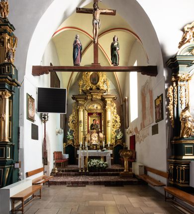 Zdjęcie nr 49: Kościół jest usytuowany w centrum wsi Rudawa, na północ od głównej drogi z Zabierzowa do Chrzanowa. Teren wokół niego jest otoczony wysokim, kamiennym murem z nieregularnych ciosów kamienia, oszkarpowanym, tynkowanym, z wyjątkiem zewnętrznej części muru na zachód od południowej bramki. W murze znajdują się trzy wejścia, od wschodu, południa i zachodu. W części wschodniej muru znajduje się trójosiowa brama wjazdowa, zwieńczona łukiem wklęsło-wypukłym, z trzema przelotami: środkowym wyższym i szerszym, zamkniętym łukiem odcinkowym i bocznymi węższymi i niższymi, zamkniętymi łukiem półkolistym (północne zamurowane). Część środkowa jest flankowana zdwojonymi pilastrami, podtrzymującymi profilowane uskokowe belkowanie z przyczółkiem o profilowanym łuku falistym, zwieńczonym równoramiennym krzyżem. W przyczółku wnęka z figurą św. Floriana. Bramki od strony zachodniej i południowej prostokątne, z przejściem zakończonym płaskim łukiem odcinkowym, z profilowanym gzymsem, zwieńczonym trójkątnym przyczółkiem. Przejścia zamykane drewnianymi ażurowymi i pomalowanymi na ciemnobrązowo jednoskrzydłowymi drzwiami. Poprzez bramkę od zachodu zejście kamiennymi schodami poprowadzonymi wzdłuż muru na dziedziniec plebański, usytuowany poniżej terenu kościelnego. 
W północno-wschodnim narożniku muru niewielka murowana i tynkowana kostnica na planie kwadratu, nakryta dachem namiotowym, łamanym, zakończonym ośmioboczną ślepą latarnią.

Po stronie południowej, poniżej placu kościelnego, do muru przylega murowana, tynkowana, prostokątna i dwukondygnacyjna „zegarowa” wieża bramna nakryta namiotowym dachem z wysoką drewnianą ośmioboczną latarnią o cebulastym hełmie. W wieży znajduje się przejazd wiodący na dziedziniec plebański, z sienią otwartą na przestrzał w dolnej kondygnacji i z lamusem dostępnym od strony placu kościelnego w górnej. 

W południowej części muru, w pobliżu południowo-wschodniego narożnika placu kościelnego, nadbudowana kamienna dzwonnica parawanowa z zawieszonymi czterema dzwonami.  

We wschodniej części placu kościelnego pomiędzy bramką wschodnią a kostnicą znajduje się kamienna ambona, o ośmiobocznej podstawie przechodzącej w szerszy, również ośmioboczny korpus, zakończony kamiennym parapetem, z kamiennymi schodami prowadzącymi na ambonę od strony wschodniej. 

Kościół jest orientowany, prawie w całości zbudowany z cegły, otynkowany z wyjątkiem prezbiterium. Wnętrze kościoła tworzy niewielkie, prostokątne, jednoprzęsłowe prezbiterium zakończone prostą ścianą i nakryte pozornym sklepieniem krzyżowo-żebrowym. Nawa jest szersza, prawie kwadratowa, nakryta drewnianym stropem. Prezbiterium z nawą są połączone szeroką, ostrołukową arkadą w ścianie tęczowej. Od północy do prezbiterium przylega założona na planie prostokąta dwuprzęsłowa zakrystia, nakryta sklepieniem krzyżowym. Wejście do zakrystii zaznaczone gotyckim, kamiennym, sfazowanym portalem zamkniętym łukiem ostrym. Od zachodu do zakrystii przylega niewielkie pomieszczenie gospodarcze, do którego z zakrystii prowadzą ostrołukowe drzwi. Zakrystia oświetlona ostrołukowym oknem w ścianie wschodniej, wypełnionym witrażem z tafelek w kształcie sześciokąta foremnego, ze szkła surowego, tzw. katedralnego. 

Od południa do nawy przylega kaplica o formach renesansowych, dwukondygnacyjna, założona na planie kwadratu. W dolnej kondygnacji sklepiona krzyżowo-żebrowo kruchta otwarta do nawy szeroką, zamkniętą półkoliście arkadą.

Ponad kruchtą kaplica św. Kazimierza, nakryta wspartą na pendentywach kopułą z latarnią. Z kruchty do kaplicy prowadzą kręte kamienne schody umieszczone od zachodu w półkolistej wieżyczce. Prostokątne wejście z krypty na klatkę schodową ujęte kamiennym profilowanym portalem. Kaplica otwarta do nawy szeroką, zamkniętą półkoliście arkadą, o kształcie i wymiarach analogicznych do arkady znajdującej się poniżej. Kaplicę, prócz latarni, oświetla prostokątne okno w ścianie południowej, wypełnione witrażem z tafelek w kształcie gomółek, ze szkła surowego, tzw. katedralnego. Na zachodniej ścianie nawy chór muzyczny, dostępny klatką schodową ukrytą w zewnętrznym aneksie przylegającym do zachodniej elewacji nawy i południowej elewacji wieży-dzwonnicy. 

Nawę i prezbiterium oświetlają umieszczone w południowych ścianach prostokątne, rozglifione okna: jedno w prezbiterium, dwa w nawie. Wszystkie wypełnione witrażami z tafelek w kształcie gomółek, ze szkła surowego, tzw. katedralnego. 

Do kościoła prowadzą dwa wejścia: poprzez arkadę z kruchty południowej oraz szerokie wejście główne prostokątne, zamknięte łukiem odcinkowym, prowadzące do kościoła z obszernej kruchty od strony zachodniej, znajdującej się w murowanym przyziemiu wieży - dzwonnicy. Kruchta, założona na planie kwadratu i nakryta murowanym stropem, doświetlona jest dwoma prostokątnymi oknami umieszczonymi naprzeciw siebie w ścianach północnej i południowej.
 
W zewnętrznej elewacji kościoła widoczny niewysoki kamienny cokół wykonany z nieregularnych ciosów kamienia. Prezbiterium, niższe od nawy, murowane z cegły w układzie wedyjskim, z domieszką układu polskiego. Wschodnie naroża prezbiterium zaakcentowane płaskimi lizenami. We wschodniej ścianie widoczny zarys zamurowanego wydłużonego okna zamkniętego lekko zaostrzonym łukiem, w trójkątnym szczycie znajduje się niewielkie wąskie okienko zakończone łukiem półkolistym. Południowa ściana prezbiterium ozdobiona fryzem z cegieł. Do ściany północnej prezbiterium przylega zakrystia, oszkarpowana, nakryta dachem pulpitowym, z dobudowanym od niej niewielkim aneksem, nakrytym takim samym zadaszeniem. Do wschodniej ściany prezbiterium przylega ogrójec nakryty dachem namiotowym z cebulastym zwieńczeniem, wspartym na sześciu smukłych, profilowanych drewnianych słupach z mieczami, pomiędzy którymi od północy i południa ażurowa drewniana balustrada. 

Nawa oszkarpowana w narożnikach. Elewacje bez podziałów architektonicznych. Od strony południowej do nawy dobudowana dwukondygnacyjna kaplica nakryta kopułą z latarnią, podzielona na dwie kondygnacje. W dolnej kondygnacji od południa wejście do kruchty zaznaczone kamiennym portalem o sfazowanych węgarach i lekko zaostrzonym łuku. Wejście zamykają drewniane dwuskrzydłowe drzwi ozdobione kratownicą z żelaznych listew. Od zachodu do kaplicy przylega półokrągła wieżyczka nakryta daszkiem stożkowym. 

Do zachodniej fasady kościoła dostawiona niska, założona na planie kwadratu trójkondygnacyjna wieża-dzwonnica: w dolnej części murowana, w narożach wzmocniona kamiennymi szkarpami, w górnej drewniana konstrukcji słupowo-ramowej z nadwieszoną izbicą i nakryta dachem półszczytowym. W dolnej, murowanej kondygnacji, na osi kościoła, prostokątne wejście do kruchty zaakcentowane przedsionkiem w kształcie ostrołukowej arkady i czterostopniowymi schodami. Przedsionek nakryty dachem dwuspadowym. Do zachodniej elewacji nawy i południowej elewacji dzwonnicy przylega niewielki, wysoki drewniany aneks, nakryty dachem pulpitowym, mieszczący klatkę schodową prowadzącą na górną kondygnację dzwonnicy i na chór muzyczny w nawie kościoła. Prostokątne wejście w południowej ścianie aneksu, do którego prowadzą pięciostopniowe proste schody. Ponad nimi, na wysokości drugiej kondygnacji dzwonnicy, niewielkie kwadratowe okno. 

Prezbiterium i nawa przykryte stromymi dachami dwuspadowymi, zamkniętymi od wschodu i zachodu szczytami sterczynowymi. Wieżyczka na sygnaturkę ośmioboczna, w dolnej części barokowa, w górnej części nowsza.