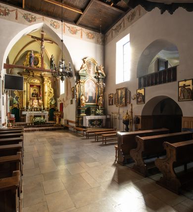 Zdjęcie nr 50: Kościół jest usytuowany w centrum wsi Rudawa, na północ od głównej drogi z Zabierzowa do Chrzanowa. Teren wokół niego jest otoczony wysokim, kamiennym murem z nieregularnych ciosów kamienia, oszkarpowanym, tynkowanym, z wyjątkiem zewnętrznej części muru na zachód od południowej bramki. W murze znajdują się trzy wejścia, od wschodu, południa i zachodu. W części wschodniej muru znajduje się trójosiowa brama wjazdowa, zwieńczona łukiem wklęsło-wypukłym, z trzema przelotami: środkowym wyższym i szerszym, zamkniętym łukiem odcinkowym i bocznymi węższymi i niższymi, zamkniętymi łukiem półkolistym (północne zamurowane). Część środkowa jest flankowana zdwojonymi pilastrami, podtrzymującymi profilowane uskokowe belkowanie z przyczółkiem o profilowanym łuku falistym, zwieńczonym równoramiennym krzyżem. W przyczółku wnęka z figurą św. Floriana. Bramki od strony zachodniej i południowej prostokątne, z przejściem zakończonym płaskim łukiem odcinkowym, z profilowanym gzymsem, zwieńczonym trójkątnym przyczółkiem. Przejścia zamykane drewnianymi ażurowymi i pomalowanymi na ciemnobrązowo jednoskrzydłowymi drzwiami. Poprzez bramkę od zachodu zejście kamiennymi schodami poprowadzonymi wzdłuż muru na dziedziniec plebański, usytuowany poniżej terenu kościelnego. 
W północno-wschodnim narożniku muru niewielka murowana i tynkowana kostnica na planie kwadratu, nakryta dachem namiotowym, łamanym, zakończonym ośmioboczną ślepą latarnią.

Po stronie południowej, poniżej placu kościelnego, do muru przylega murowana, tynkowana, prostokątna i dwukondygnacyjna „zegarowa” wieża bramna nakryta namiotowym dachem z wysoką drewnianą ośmioboczną latarnią o cebulastym hełmie. W wieży znajduje się przejazd wiodący na dziedziniec plebański, z sienią otwartą na przestrzał w dolnej kondygnacji i z lamusem dostępnym od strony placu kościelnego w górnej. 

W południowej części muru, w pobliżu południowo-wschodniego narożnika placu kościelnego, nadbudowana kamienna dzwonnica parawanowa z zawieszonymi czterema dzwonami.  

We wschodniej części placu kościelnego pomiędzy bramką wschodnią a kostnicą znajduje się kamienna ambona, o ośmiobocznej podstawie przechodzącej w szerszy, również ośmioboczny korpus, zakończony kamiennym parapetem, z kamiennymi schodami prowadzącymi na ambonę od strony wschodniej. 

Kościół jest orientowany, prawie w całości zbudowany z cegły, otynkowany z wyjątkiem prezbiterium. Wnętrze kościoła tworzy niewielkie, prostokątne, jednoprzęsłowe prezbiterium zakończone prostą ścianą i nakryte pozornym sklepieniem krzyżowo-żebrowym. Nawa jest szersza, prawie kwadratowa, nakryta drewnianym stropem. Prezbiterium z nawą są połączone szeroką, ostrołukową arkadą w ścianie tęczowej. Od północy do prezbiterium przylega założona na planie prostokąta dwuprzęsłowa zakrystia, nakryta sklepieniem krzyżowym. Wejście do zakrystii zaznaczone gotyckim, kamiennym, sfazowanym portalem zamkniętym łukiem ostrym. Od zachodu do zakrystii przylega niewielkie pomieszczenie gospodarcze, do którego z zakrystii prowadzą ostrołukowe drzwi. Zakrystia oświetlona ostrołukowym oknem w ścianie wschodniej, wypełnionym witrażem z tafelek w kształcie sześciokąta foremnego, ze szkła surowego, tzw. katedralnego. 

Od południa do nawy przylega kaplica o formach renesansowych, dwukondygnacyjna, założona na planie kwadratu. W dolnej kondygnacji sklepiona krzyżowo-żebrowo kruchta otwarta do nawy szeroką, zamkniętą półkoliście arkadą.

Ponad kruchtą kaplica św. Kazimierza, nakryta wspartą na pendentywach kopułą z latarnią. Z kruchty do kaplicy prowadzą kręte kamienne schody umieszczone od zachodu w półkolistej wieżyczce. Prostokątne wejście z krypty na klatkę schodową ujęte kamiennym profilowanym portalem. Kaplica otwarta do nawy szeroką, zamkniętą półkoliście arkadą, o kształcie i wymiarach analogicznych do arkady znajdującej się poniżej. Kaplicę, prócz latarni, oświetla prostokątne okno w ścianie południowej, wypełnione witrażem z tafelek w kształcie gomółek, ze szkła surowego, tzw. katedralnego. Na zachodniej ścianie nawy chór muzyczny, dostępny klatką schodową ukrytą w zewnętrznym aneksie przylegającym do zachodniej elewacji nawy i południowej elewacji wieży-dzwonnicy. 

Nawę i prezbiterium oświetlają umieszczone w południowych ścianach prostokątne, rozglifione okna: jedno w prezbiterium, dwa w nawie. Wszystkie wypełnione witrażami z tafelek w kształcie gomółek, ze szkła surowego, tzw. katedralnego. 

Do kościoła prowadzą dwa wejścia: poprzez arkadę z kruchty południowej oraz szerokie wejście główne prostokątne, zamknięte łukiem odcinkowym, prowadzące do kościoła z obszernej kruchty od strony zachodniej, znajdującej się w murowanym przyziemiu wieży - dzwonnicy. Kruchta, założona na planie kwadratu i nakryta murowanym stropem, doświetlona jest dwoma prostokątnymi oknami umieszczonymi naprzeciw siebie w ścianach północnej i południowej.
 
W zewnętrznej elewacji kościoła widoczny niewysoki kamienny cokół wykonany z nieregularnych ciosów kamienia. Prezbiterium, niższe od nawy, murowane z cegły w układzie wedyjskim, z domieszką układu polskiego. Wschodnie naroża prezbiterium zaakcentowane płaskimi lizenami. We wschodniej ścianie widoczny zarys zamurowanego wydłużonego okna zamkniętego lekko zaostrzonym łukiem, w trójkątnym szczycie znajduje się niewielkie wąskie okienko zakończone łukiem półkolistym. Południowa ściana prezbiterium ozdobiona fryzem z cegieł. Do ściany północnej prezbiterium przylega zakrystia, oszkarpowana, nakryta dachem pulpitowym, z dobudowanym od niej niewielkim aneksem, nakrytym takim samym zadaszeniem. Do wschodniej ściany prezbiterium przylega ogrójec nakryty dachem namiotowym z cebulastym zwieńczeniem, wspartym na sześciu smukłych, profilowanych drewnianych słupach z mieczami, pomiędzy którymi od północy i południa ażurowa drewniana balustrada. 

Nawa oszkarpowana w narożnikach. Elewacje bez podziałów architektonicznych. Od strony południowej do nawy dobudowana dwukondygnacyjna kaplica nakryta kopułą z latarnią, podzielona na dwie kondygnacje. W dolnej kondygnacji od południa wejście do kruchty zaznaczone kamiennym portalem o sfazowanych węgarach i lekko zaostrzonym łuku. Wejście zamykają drewniane dwuskrzydłowe drzwi ozdobione kratownicą z żelaznych listew. Od zachodu do kaplicy przylega półokrągła wieżyczka nakryta daszkiem stożkowym. 

Do zachodniej fasady kościoła dostawiona niska, założona na planie kwadratu trójkondygnacyjna wieża-dzwonnica: w dolnej części murowana, w narożach wzmocniona kamiennymi szkarpami, w górnej drewniana konstrukcji słupowo-ramowej z nadwieszoną izbicą i nakryta dachem półszczytowym. W dolnej, murowanej kondygnacji, na osi kościoła, prostokątne wejście do kruchty zaakcentowane przedsionkiem w kształcie ostrołukowej arkady i czterostopniowymi schodami. Przedsionek nakryty dachem dwuspadowym. Do zachodniej elewacji nawy i południowej elewacji dzwonnicy przylega niewielki, wysoki drewniany aneks, nakryty dachem pulpitowym, mieszczący klatkę schodową prowadzącą na górną kondygnację dzwonnicy i na chór muzyczny w nawie kościoła. Prostokątne wejście w południowej ścianie aneksu, do którego prowadzą pięciostopniowe proste schody. Ponad nimi, na wysokości drugiej kondygnacji dzwonnicy, niewielkie kwadratowe okno. 

Prezbiterium i nawa przykryte stromymi dachami dwuspadowymi, zamkniętymi od wschodu i zachodu szczytami sterczynowymi. Wieżyczka na sygnaturkę ośmioboczna, w dolnej części barokowa, w górnej części nowsza.