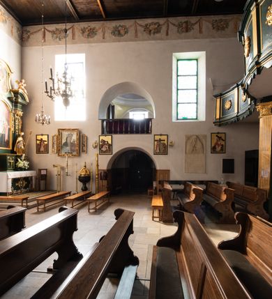 Zdjęcie nr 52: Kościół jest usytuowany w centrum wsi Rudawa, na północ od głównej drogi z Zabierzowa do Chrzanowa. Teren wokół niego jest otoczony wysokim, kamiennym murem z nieregularnych ciosów kamienia, oszkarpowanym, tynkowanym, z wyjątkiem zewnętrznej części muru na zachód od południowej bramki. W murze znajdują się trzy wejścia, od wschodu, południa i zachodu. W części wschodniej muru znajduje się trójosiowa brama wjazdowa, zwieńczona łukiem wklęsło-wypukłym, z trzema przelotami: środkowym wyższym i szerszym, zamkniętym łukiem odcinkowym i bocznymi węższymi i niższymi, zamkniętymi łukiem półkolistym (północne zamurowane). Część środkowa jest flankowana zdwojonymi pilastrami, podtrzymującymi profilowane uskokowe belkowanie z przyczółkiem o profilowanym łuku falistym, zwieńczonym równoramiennym krzyżem. W przyczółku wnęka z figurą św. Floriana. Bramki od strony zachodniej i południowej prostokątne, z przejściem zakończonym płaskim łukiem odcinkowym, z profilowanym gzymsem, zwieńczonym trójkątnym przyczółkiem. Przejścia zamykane drewnianymi ażurowymi i pomalowanymi na ciemnobrązowo jednoskrzydłowymi drzwiami. Poprzez bramkę od zachodu zejście kamiennymi schodami poprowadzonymi wzdłuż muru na dziedziniec plebański, usytuowany poniżej terenu kościelnego. 
W północno-wschodnim narożniku muru niewielka murowana i tynkowana kostnica na planie kwadratu, nakryta dachem namiotowym, łamanym, zakończonym ośmioboczną ślepą latarnią.

Po stronie południowej, poniżej placu kościelnego, do muru przylega murowana, tynkowana, prostokątna i dwukondygnacyjna „zegarowa” wieża bramna nakryta namiotowym dachem z wysoką drewnianą ośmioboczną latarnią o cebulastym hełmie. W wieży znajduje się przejazd wiodący na dziedziniec plebański, z sienią otwartą na przestrzał w dolnej kondygnacji i z lamusem dostępnym od strony placu kościelnego w górnej. 

W południowej części muru, w pobliżu południowo-wschodniego narożnika placu kościelnego, nadbudowana kamienna dzwonnica parawanowa z zawieszonymi czterema dzwonami.  

We wschodniej części placu kościelnego pomiędzy bramką wschodnią a kostnicą znajduje się kamienna ambona, o ośmiobocznej podstawie przechodzącej w szerszy, również ośmioboczny korpus, zakończony kamiennym parapetem, z kamiennymi schodami prowadzącymi na ambonę od strony wschodniej. 

Kościół jest orientowany, prawie w całości zbudowany z cegły, otynkowany z wyjątkiem prezbiterium. Wnętrze kościoła tworzy niewielkie, prostokątne, jednoprzęsłowe prezbiterium zakończone prostą ścianą i nakryte pozornym sklepieniem krzyżowo-żebrowym. Nawa jest szersza, prawie kwadratowa, nakryta drewnianym stropem. Prezbiterium z nawą są połączone szeroką, ostrołukową arkadą w ścianie tęczowej. Od północy do prezbiterium przylega założona na planie prostokąta dwuprzęsłowa zakrystia, nakryta sklepieniem krzyżowym. Wejście do zakrystii zaznaczone gotyckim, kamiennym, sfazowanym portalem zamkniętym łukiem ostrym. Od zachodu do zakrystii przylega niewielkie pomieszczenie gospodarcze, do którego z zakrystii prowadzą ostrołukowe drzwi. Zakrystia oświetlona ostrołukowym oknem w ścianie wschodniej, wypełnionym witrażem z tafelek w kształcie sześciokąta foremnego, ze szkła surowego, tzw. katedralnego. 

Od południa do nawy przylega kaplica o formach renesansowych, dwukondygnacyjna, założona na planie kwadratu. W dolnej kondygnacji sklepiona krzyżowo-żebrowo kruchta otwarta do nawy szeroką, zamkniętą półkoliście arkadą.

Ponad kruchtą kaplica św. Kazimierza, nakryta wspartą na pendentywach kopułą z latarnią. Z kruchty do kaplicy prowadzą kręte kamienne schody umieszczone od zachodu w półkolistej wieżyczce. Prostokątne wejście z krypty na klatkę schodową ujęte kamiennym profilowanym portalem. Kaplica otwarta do nawy szeroką, zamkniętą półkoliście arkadą, o kształcie i wymiarach analogicznych do arkady znajdującej się poniżej. Kaplicę, prócz latarni, oświetla prostokątne okno w ścianie południowej, wypełnione witrażem z tafelek w kształcie gomółek, ze szkła surowego, tzw. katedralnego. Na zachodniej ścianie nawy chór muzyczny, dostępny klatką schodową ukrytą w zewnętrznym aneksie przylegającym do zachodniej elewacji nawy i południowej elewacji wieży-dzwonnicy. 

Nawę i prezbiterium oświetlają umieszczone w południowych ścianach prostokątne, rozglifione okna: jedno w prezbiterium, dwa w nawie. Wszystkie wypełnione witrażami z tafelek w kształcie gomółek, ze szkła surowego, tzw. katedralnego. 

Do kościoła prowadzą dwa wejścia: poprzez arkadę z kruchty południowej oraz szerokie wejście główne prostokątne, zamknięte łukiem odcinkowym, prowadzące do kościoła z obszernej kruchty od strony zachodniej, znajdującej się w murowanym przyziemiu wieży - dzwonnicy. Kruchta, założona na planie kwadratu i nakryta murowanym stropem, doświetlona jest dwoma prostokątnymi oknami umieszczonymi naprzeciw siebie w ścianach północnej i południowej.
 
W zewnętrznej elewacji kościoła widoczny niewysoki kamienny cokół wykonany z nieregularnych ciosów kamienia. Prezbiterium, niższe od nawy, murowane z cegły w układzie wedyjskim, z domieszką układu polskiego. Wschodnie naroża prezbiterium zaakcentowane płaskimi lizenami. We wschodniej ścianie widoczny zarys zamurowanego wydłużonego okna zamkniętego lekko zaostrzonym łukiem, w trójkątnym szczycie znajduje się niewielkie wąskie okienko zakończone łukiem półkolistym. Południowa ściana prezbiterium ozdobiona fryzem z cegieł. Do ściany północnej prezbiterium przylega zakrystia, oszkarpowana, nakryta dachem pulpitowym, z dobudowanym od niej niewielkim aneksem, nakrytym takim samym zadaszeniem. Do wschodniej ściany prezbiterium przylega ogrójec nakryty dachem namiotowym z cebulastym zwieńczeniem, wspartym na sześciu smukłych, profilowanych drewnianych słupach z mieczami, pomiędzy którymi od północy i południa ażurowa drewniana balustrada. 

Nawa oszkarpowana w narożnikach. Elewacje bez podziałów architektonicznych. Od strony południowej do nawy dobudowana dwukondygnacyjna kaplica nakryta kopułą z latarnią, podzielona na dwie kondygnacje. W dolnej kondygnacji od południa wejście do kruchty zaznaczone kamiennym portalem o sfazowanych węgarach i lekko zaostrzonym łuku. Wejście zamykają drewniane dwuskrzydłowe drzwi ozdobione kratownicą z żelaznych listew. Od zachodu do kaplicy przylega półokrągła wieżyczka nakryta daszkiem stożkowym. 

Do zachodniej fasady kościoła dostawiona niska, założona na planie kwadratu trójkondygnacyjna wieża-dzwonnica: w dolnej części murowana, w narożach wzmocniona kamiennymi szkarpami, w górnej drewniana konstrukcji słupowo-ramowej z nadwieszoną izbicą i nakryta dachem półszczytowym. W dolnej, murowanej kondygnacji, na osi kościoła, prostokątne wejście do kruchty zaakcentowane przedsionkiem w kształcie ostrołukowej arkady i czterostopniowymi schodami. Przedsionek nakryty dachem dwuspadowym. Do zachodniej elewacji nawy i południowej elewacji dzwonnicy przylega niewielki, wysoki drewniany aneks, nakryty dachem pulpitowym, mieszczący klatkę schodową prowadzącą na górną kondygnację dzwonnicy i na chór muzyczny w nawie kościoła. Prostokątne wejście w południowej ścianie aneksu, do którego prowadzą pięciostopniowe proste schody. Ponad nimi, na wysokości drugiej kondygnacji dzwonnicy, niewielkie kwadratowe okno. 

Prezbiterium i nawa przykryte stromymi dachami dwuspadowymi, zamkniętymi od wschodu i zachodu szczytami sterczynowymi. Wieżyczka na sygnaturkę ośmioboczna, w dolnej części barokowa, w górnej części nowsza.