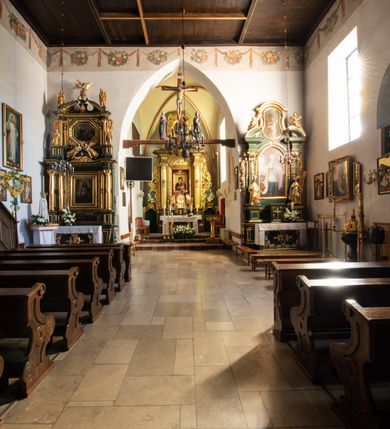 Zdjęcie nr 53: Kościół jest usytuowany w centrum wsi Rudawa, na północ od głównej drogi z Zabierzowa do Chrzanowa. Teren wokół niego jest otoczony wysokim, kamiennym murem z nieregularnych ciosów kamienia, oszkarpowanym, tynkowanym, z wyjątkiem zewnętrznej części muru na zachód od południowej bramki. W murze znajdują się trzy wejścia, od wschodu, południa i zachodu. W części wschodniej muru znajduje się trójosiowa brama wjazdowa, zwieńczona łukiem wklęsło-wypukłym, z trzema przelotami: środkowym wyższym i szerszym, zamkniętym łukiem odcinkowym i bocznymi węższymi i niższymi, zamkniętymi łukiem półkolistym (północne zamurowane). Część środkowa jest flankowana zdwojonymi pilastrami, podtrzymującymi profilowane uskokowe belkowanie z przyczółkiem o profilowanym łuku falistym, zwieńczonym równoramiennym krzyżem. W przyczółku wnęka z figurą św. Floriana. Bramki od strony zachodniej i południowej prostokątne, z przejściem zakończonym płaskim łukiem odcinkowym, z profilowanym gzymsem, zwieńczonym trójkątnym przyczółkiem. Przejścia zamykane drewnianymi ażurowymi i pomalowanymi na ciemnobrązowo jednoskrzydłowymi drzwiami. Poprzez bramkę od zachodu zejście kamiennymi schodami poprowadzonymi wzdłuż muru na dziedziniec plebański, usytuowany poniżej terenu kościelnego. 
W północno-wschodnim narożniku muru niewielka murowana i tynkowana kostnica na planie kwadratu, nakryta dachem namiotowym, łamanym, zakończonym ośmioboczną ślepą latarnią.

Po stronie południowej, poniżej placu kościelnego, do muru przylega murowana, tynkowana, prostokątna i dwukondygnacyjna „zegarowa” wieża bramna nakryta namiotowym dachem z wysoką drewnianą ośmioboczną latarnią o cebulastym hełmie. W wieży znajduje się przejazd wiodący na dziedziniec plebański, z sienią otwartą na przestrzał w dolnej kondygnacji i z lamusem dostępnym od strony placu kościelnego w górnej. 

W południowej części muru, w pobliżu południowo-wschodniego narożnika placu kościelnego, nadbudowana kamienna dzwonnica parawanowa z zawieszonymi czterema dzwonami.  

We wschodniej części placu kościelnego pomiędzy bramką wschodnią a kostnicą znajduje się kamienna ambona, o ośmiobocznej podstawie przechodzącej w szerszy, również ośmioboczny korpus, zakończony kamiennym parapetem, z kamiennymi schodami prowadzącymi na ambonę od strony wschodniej. 

Kościół jest orientowany, prawie w całości zbudowany z cegły, otynkowany z wyjątkiem prezbiterium. Wnętrze kościoła tworzy niewielkie, prostokątne, jednoprzęsłowe prezbiterium zakończone prostą ścianą i nakryte pozornym sklepieniem krzyżowo-żebrowym. Nawa jest szersza, prawie kwadratowa, nakryta drewnianym stropem. Prezbiterium z nawą są połączone szeroką, ostrołukową arkadą w ścianie tęczowej. Od północy do prezbiterium przylega założona na planie prostokąta dwuprzęsłowa zakrystia, nakryta sklepieniem krzyżowym. Wejście do zakrystii zaznaczone gotyckim, kamiennym, sfazowanym portalem zamkniętym łukiem ostrym. Od zachodu do zakrystii przylega niewielkie pomieszczenie gospodarcze, do którego z zakrystii prowadzą ostrołukowe drzwi. Zakrystia oświetlona ostrołukowym oknem w ścianie wschodniej, wypełnionym witrażem z tafelek w kształcie sześciokąta foremnego, ze szkła surowego, tzw. katedralnego. 

Od południa do nawy przylega kaplica o formach renesansowych, dwukondygnacyjna, założona na planie kwadratu. W dolnej kondygnacji sklepiona krzyżowo-żebrowo kruchta otwarta do nawy szeroką, zamkniętą półkoliście arkadą.

Ponad kruchtą kaplica św. Kazimierza, nakryta wspartą na pendentywach kopułą z latarnią. Z kruchty do kaplicy prowadzą kręte kamienne schody umieszczone od zachodu w półkolistej wieżyczce. Prostokątne wejście z krypty na klatkę schodową ujęte kamiennym profilowanym portalem. Kaplica otwarta do nawy szeroką, zamkniętą półkoliście arkadą, o kształcie i wymiarach analogicznych do arkady znajdującej się poniżej. Kaplicę, prócz latarni, oświetla prostokątne okno w ścianie południowej, wypełnione witrażem z tafelek w kształcie gomółek, ze szkła surowego, tzw. katedralnego. Na zachodniej ścianie nawy chór muzyczny, dostępny klatką schodową ukrytą w zewnętrznym aneksie przylegającym do zachodniej elewacji nawy i południowej elewacji wieży-dzwonnicy. 

Nawę i prezbiterium oświetlają umieszczone w południowych ścianach prostokątne, rozglifione okna: jedno w prezbiterium, dwa w nawie. Wszystkie wypełnione witrażami z tafelek w kształcie gomółek, ze szkła surowego, tzw. katedralnego. 

Do kościoła prowadzą dwa wejścia: poprzez arkadę z kruchty południowej oraz szerokie wejście główne prostokątne, zamknięte łukiem odcinkowym, prowadzące do kościoła z obszernej kruchty od strony zachodniej, znajdującej się w murowanym przyziemiu wieży - dzwonnicy. Kruchta, założona na planie kwadratu i nakryta murowanym stropem, doświetlona jest dwoma prostokątnymi oknami umieszczonymi naprzeciw siebie w ścianach północnej i południowej.
 
W zewnętrznej elewacji kościoła widoczny niewysoki kamienny cokół wykonany z nieregularnych ciosów kamienia. Prezbiterium, niższe od nawy, murowane z cegły w układzie wedyjskim, z domieszką układu polskiego. Wschodnie naroża prezbiterium zaakcentowane płaskimi lizenami. We wschodniej ścianie widoczny zarys zamurowanego wydłużonego okna zamkniętego lekko zaostrzonym łukiem, w trójkątnym szczycie znajduje się niewielkie wąskie okienko zakończone łukiem półkolistym. Południowa ściana prezbiterium ozdobiona fryzem z cegieł. Do ściany północnej prezbiterium przylega zakrystia, oszkarpowana, nakryta dachem pulpitowym, z dobudowanym od niej niewielkim aneksem, nakrytym takim samym zadaszeniem. Do wschodniej ściany prezbiterium przylega ogrójec nakryty dachem namiotowym z cebulastym zwieńczeniem, wspartym na sześciu smukłych, profilowanych drewnianych słupach z mieczami, pomiędzy którymi od północy i południa ażurowa drewniana balustrada. 

Nawa oszkarpowana w narożnikach. Elewacje bez podziałów architektonicznych. Od strony południowej do nawy dobudowana dwukondygnacyjna kaplica nakryta kopułą z latarnią, podzielona na dwie kondygnacje. W dolnej kondygnacji od południa wejście do kruchty zaznaczone kamiennym portalem o sfazowanych węgarach i lekko zaostrzonym łuku. Wejście zamykają drewniane dwuskrzydłowe drzwi ozdobione kratownicą z żelaznych listew. Od zachodu do kaplicy przylega półokrągła wieżyczka nakryta daszkiem stożkowym. 

Do zachodniej fasady kościoła dostawiona niska, założona na planie kwadratu trójkondygnacyjna wieża-dzwonnica: w dolnej części murowana, w narożach wzmocniona kamiennymi szkarpami, w górnej drewniana konstrukcji słupowo-ramowej z nadwieszoną izbicą i nakryta dachem półszczytowym. W dolnej, murowanej kondygnacji, na osi kościoła, prostokątne wejście do kruchty zaakcentowane przedsionkiem w kształcie ostrołukowej arkady i czterostopniowymi schodami. Przedsionek nakryty dachem dwuspadowym. Do zachodniej elewacji nawy i południowej elewacji dzwonnicy przylega niewielki, wysoki drewniany aneks, nakryty dachem pulpitowym, mieszczący klatkę schodową prowadzącą na górną kondygnację dzwonnicy i na chór muzyczny w nawie kościoła. Prostokątne wejście w południowej ścianie aneksu, do którego prowadzą pięciostopniowe proste schody. Ponad nimi, na wysokości drugiej kondygnacji dzwonnicy, niewielkie kwadratowe okno. 

Prezbiterium i nawa przykryte stromymi dachami dwuspadowymi, zamkniętymi od wschodu i zachodu szczytami sterczynowymi. Wieżyczka na sygnaturkę ośmioboczna, w dolnej części barokowa, w górnej części nowsza.