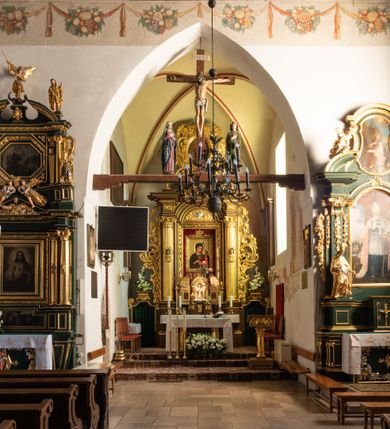 Zdjęcie nr 56: Kościół jest usytuowany w centrum wsi Rudawa, na północ od głównej drogi z Zabierzowa do Chrzanowa. Teren wokół niego jest otoczony wysokim, kamiennym murem z nieregularnych ciosów kamienia, oszkarpowanym, tynkowanym, z wyjątkiem zewnętrznej części muru na zachód od południowej bramki. W murze znajdują się trzy wejścia, od wschodu, południa i zachodu. W części wschodniej muru znajduje się trójosiowa brama wjazdowa, zwieńczona łukiem wklęsło-wypukłym, z trzema przelotami: środkowym wyższym i szerszym, zamkniętym łukiem odcinkowym i bocznymi węższymi i niższymi, zamkniętymi łukiem półkolistym (północne zamurowane). Część środkowa jest flankowana zdwojonymi pilastrami, podtrzymującymi profilowane uskokowe belkowanie z przyczółkiem o profilowanym łuku falistym, zwieńczonym równoramiennym krzyżem. W przyczółku wnęka z figurą św. Floriana. Bramki od strony zachodniej i południowej prostokątne, z przejściem zakończonym płaskim łukiem odcinkowym, z profilowanym gzymsem, zwieńczonym trójkątnym przyczółkiem. Przejścia zamykane drewnianymi ażurowymi i pomalowanymi na ciemnobrązowo jednoskrzydłowymi drzwiami. Poprzez bramkę od zachodu zejście kamiennymi schodami poprowadzonymi wzdłuż muru na dziedziniec plebański, usytuowany poniżej terenu kościelnego. 
W północno-wschodnim narożniku muru niewielka murowana i tynkowana kostnica na planie kwadratu, nakryta dachem namiotowym, łamanym, zakończonym ośmioboczną ślepą latarnią.

Po stronie południowej, poniżej placu kościelnego, do muru przylega murowana, tynkowana, prostokątna i dwukondygnacyjna „zegarowa” wieża bramna nakryta namiotowym dachem z wysoką drewnianą ośmioboczną latarnią o cebulastym hełmie. W wieży znajduje się przejazd wiodący na dziedziniec plebański, z sienią otwartą na przestrzał w dolnej kondygnacji i z lamusem dostępnym od strony placu kościelnego w górnej. 

W południowej części muru, w pobliżu południowo-wschodniego narożnika placu kościelnego, nadbudowana kamienna dzwonnica parawanowa z zawieszonymi czterema dzwonami.  

We wschodniej części placu kościelnego pomiędzy bramką wschodnią a kostnicą znajduje się kamienna ambona, o ośmiobocznej podstawie przechodzącej w szerszy, również ośmioboczny korpus, zakończony kamiennym parapetem, z kamiennymi schodami prowadzącymi na ambonę od strony wschodniej. 

Kościół jest orientowany, prawie w całości zbudowany z cegły, otynkowany z wyjątkiem prezbiterium. Wnętrze kościoła tworzy niewielkie, prostokątne, jednoprzęsłowe prezbiterium zakończone prostą ścianą i nakryte pozornym sklepieniem krzyżowo-żebrowym. Nawa jest szersza, prawie kwadratowa, nakryta drewnianym stropem. Prezbiterium z nawą są połączone szeroką, ostrołukową arkadą w ścianie tęczowej. Od północy do prezbiterium przylega założona na planie prostokąta dwuprzęsłowa zakrystia, nakryta sklepieniem krzyżowym. Wejście do zakrystii zaznaczone gotyckim, kamiennym, sfazowanym portalem zamkniętym łukiem ostrym. Od zachodu do zakrystii przylega niewielkie pomieszczenie gospodarcze, do którego z zakrystii prowadzą ostrołukowe drzwi. Zakrystia oświetlona ostrołukowym oknem w ścianie wschodniej, wypełnionym witrażem z tafelek w kształcie sześciokąta foremnego, ze szkła surowego, tzw. katedralnego. 

Od południa do nawy przylega kaplica o formach renesansowych, dwukondygnacyjna, założona na planie kwadratu. W dolnej kondygnacji sklepiona krzyżowo-żebrowo kruchta otwarta do nawy szeroką, zamkniętą półkoliście arkadą.

Ponad kruchtą kaplica św. Kazimierza, nakryta wspartą na pendentywach kopułą z latarnią. Z kruchty do kaplicy prowadzą kręte kamienne schody umieszczone od zachodu w półkolistej wieżyczce. Prostokątne wejście z krypty na klatkę schodową ujęte kamiennym profilowanym portalem. Kaplica otwarta do nawy szeroką, zamkniętą półkoliście arkadą, o kształcie i wymiarach analogicznych do arkady znajdującej się poniżej. Kaplicę, prócz latarni, oświetla prostokątne okno w ścianie południowej, wypełnione witrażem z tafelek w kształcie gomółek, ze szkła surowego, tzw. katedralnego. Na zachodniej ścianie nawy chór muzyczny, dostępny klatką schodową ukrytą w zewnętrznym aneksie przylegającym do zachodniej elewacji nawy i południowej elewacji wieży-dzwonnicy. 

Nawę i prezbiterium oświetlają umieszczone w południowych ścianach prostokątne, rozglifione okna: jedno w prezbiterium, dwa w nawie. Wszystkie wypełnione witrażami z tafelek w kształcie gomółek, ze szkła surowego, tzw. katedralnego. 

Do kościoła prowadzą dwa wejścia: poprzez arkadę z kruchty południowej oraz szerokie wejście główne prostokątne, zamknięte łukiem odcinkowym, prowadzące do kościoła z obszernej kruchty od strony zachodniej, znajdującej się w murowanym przyziemiu wieży - dzwonnicy. Kruchta, założona na planie kwadratu i nakryta murowanym stropem, doświetlona jest dwoma prostokątnymi oknami umieszczonymi naprzeciw siebie w ścianach północnej i południowej.
 
W zewnętrznej elewacji kościoła widoczny niewysoki kamienny cokół wykonany z nieregularnych ciosów kamienia. Prezbiterium, niższe od nawy, murowane z cegły w układzie wedyjskim, z domieszką układu polskiego. Wschodnie naroża prezbiterium zaakcentowane płaskimi lizenami. We wschodniej ścianie widoczny zarys zamurowanego wydłużonego okna zamkniętego lekko zaostrzonym łukiem, w trójkątnym szczycie znajduje się niewielkie wąskie okienko zakończone łukiem półkolistym. Południowa ściana prezbiterium ozdobiona fryzem z cegieł. Do ściany północnej prezbiterium przylega zakrystia, oszkarpowana, nakryta dachem pulpitowym, z dobudowanym od niej niewielkim aneksem, nakrytym takim samym zadaszeniem. Do wschodniej ściany prezbiterium przylega ogrójec nakryty dachem namiotowym z cebulastym zwieńczeniem, wspartym na sześciu smukłych, profilowanych drewnianych słupach z mieczami, pomiędzy którymi od północy i południa ażurowa drewniana balustrada. 

Nawa oszkarpowana w narożnikach. Elewacje bez podziałów architektonicznych. Od strony południowej do nawy dobudowana dwukondygnacyjna kaplica nakryta kopułą z latarnią, podzielona na dwie kondygnacje. W dolnej kondygnacji od południa wejście do kruchty zaznaczone kamiennym portalem o sfazowanych węgarach i lekko zaostrzonym łuku. Wejście zamykają drewniane dwuskrzydłowe drzwi ozdobione kratownicą z żelaznych listew. Od zachodu do kaplicy przylega półokrągła wieżyczka nakryta daszkiem stożkowym. 

Do zachodniej fasady kościoła dostawiona niska, założona na planie kwadratu trójkondygnacyjna wieża-dzwonnica: w dolnej części murowana, w narożach wzmocniona kamiennymi szkarpami, w górnej drewniana konstrukcji słupowo-ramowej z nadwieszoną izbicą i nakryta dachem półszczytowym. W dolnej, murowanej kondygnacji, na osi kościoła, prostokątne wejście do kruchty zaakcentowane przedsionkiem w kształcie ostrołukowej arkady i czterostopniowymi schodami. Przedsionek nakryty dachem dwuspadowym. Do zachodniej elewacji nawy i południowej elewacji dzwonnicy przylega niewielki, wysoki drewniany aneks, nakryty dachem pulpitowym, mieszczący klatkę schodową prowadzącą na górną kondygnację dzwonnicy i na chór muzyczny w nawie kościoła. Prostokątne wejście w południowej ścianie aneksu, do którego prowadzą pięciostopniowe proste schody. Ponad nimi, na wysokości drugiej kondygnacji dzwonnicy, niewielkie kwadratowe okno. 

Prezbiterium i nawa przykryte stromymi dachami dwuspadowymi, zamkniętymi od wschodu i zachodu szczytami sterczynowymi. Wieżyczka na sygnaturkę ośmioboczna, w dolnej części barokowa, w górnej części nowsza.