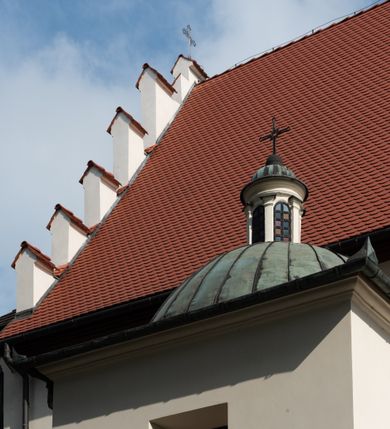 Zdjęcie nr 58: Kościół jest usytuowany w centrum wsi Rudawa, na północ od głównej drogi z Zabierzowa do Chrzanowa. Teren wokół niego jest otoczony wysokim, kamiennym murem z nieregularnych ciosów kamienia, oszkarpowanym, tynkowanym, z wyjątkiem zewnętrznej części muru na zachód od południowej bramki. W murze znajdują się trzy wejścia, od wschodu, południa i zachodu. W części wschodniej muru znajduje się trójosiowa brama wjazdowa, zwieńczona łukiem wklęsło-wypukłym, z trzema przelotami: środkowym wyższym i szerszym, zamkniętym łukiem odcinkowym i bocznymi węższymi i niższymi, zamkniętymi łukiem półkolistym (północne zamurowane). Część środkowa jest flankowana zdwojonymi pilastrami, podtrzymującymi profilowane uskokowe belkowanie z przyczółkiem o profilowanym łuku falistym, zwieńczonym równoramiennym krzyżem. W przyczółku wnęka z figurą św. Floriana. Bramki od strony zachodniej i południowej prostokątne, z przejściem zakończonym płaskim łukiem odcinkowym, z profilowanym gzymsem, zwieńczonym trójkątnym przyczółkiem. Przejścia zamykane drewnianymi ażurowymi i pomalowanymi na ciemnobrązowo jednoskrzydłowymi drzwiami. Poprzez bramkę od zachodu zejście kamiennymi schodami poprowadzonymi wzdłuż muru na dziedziniec plebański, usytuowany poniżej terenu kościelnego. 
W północno-wschodnim narożniku muru niewielka murowana i tynkowana kostnica na planie kwadratu, nakryta dachem namiotowym, łamanym, zakończonym ośmioboczną ślepą latarnią.

Po stronie południowej, poniżej placu kościelnego, do muru przylega murowana, tynkowana, prostokątna i dwukondygnacyjna „zegarowa” wieża bramna nakryta namiotowym dachem z wysoką drewnianą ośmioboczną latarnią o cebulastym hełmie. W wieży znajduje się przejazd wiodący na dziedziniec plebański, z sienią otwartą na przestrzał w dolnej kondygnacji i z lamusem dostępnym od strony placu kościelnego w górnej. 

W południowej części muru, w pobliżu południowo-wschodniego narożnika placu kościelnego, nadbudowana kamienna dzwonnica parawanowa z zawieszonymi czterema dzwonami.  

We wschodniej części placu kościelnego pomiędzy bramką wschodnią a kostnicą znajduje się kamienna ambona, o ośmiobocznej podstawie przechodzącej w szerszy, również ośmioboczny korpus, zakończony kamiennym parapetem, z kamiennymi schodami prowadzącymi na ambonę od strony wschodniej. 

Kościół jest orientowany, prawie w całości zbudowany z cegły, otynkowany z wyjątkiem prezbiterium. Wnętrze kościoła tworzy niewielkie, prostokątne, jednoprzęsłowe prezbiterium zakończone prostą ścianą i nakryte pozornym sklepieniem krzyżowo-żebrowym. Nawa jest szersza, prawie kwadratowa, nakryta drewnianym stropem. Prezbiterium z nawą są połączone szeroką, ostrołukową arkadą w ścianie tęczowej. Od północy do prezbiterium przylega założona na planie prostokąta dwuprzęsłowa zakrystia, nakryta sklepieniem krzyżowym. Wejście do zakrystii zaznaczone gotyckim, kamiennym, sfazowanym portalem zamkniętym łukiem ostrym. Od zachodu do zakrystii przylega niewielkie pomieszczenie gospodarcze, do którego z zakrystii prowadzą ostrołukowe drzwi. Zakrystia oświetlona ostrołukowym oknem w ścianie wschodniej, wypełnionym witrażem z tafelek w kształcie sześciokąta foremnego, ze szkła surowego, tzw. katedralnego. 

Od południa do nawy przylega kaplica o formach renesansowych, dwukondygnacyjna, założona na planie kwadratu. W dolnej kondygnacji sklepiona krzyżowo-żebrowo kruchta otwarta do nawy szeroką, zamkniętą półkoliście arkadą.

Ponad kruchtą kaplica św. Kazimierza, nakryta wspartą na pendentywach kopułą z latarnią. Z kruchty do kaplicy prowadzą kręte kamienne schody umieszczone od zachodu w półkolistej wieżyczce. Prostokątne wejście z krypty na klatkę schodową ujęte kamiennym profilowanym portalem. Kaplica otwarta do nawy szeroką, zamkniętą półkoliście arkadą, o kształcie i wymiarach analogicznych do arkady znajdującej się poniżej. Kaplicę, prócz latarni, oświetla prostokątne okno w ścianie południowej, wypełnione witrażem z tafelek w kształcie gomółek, ze szkła surowego, tzw. katedralnego. Na zachodniej ścianie nawy chór muzyczny, dostępny klatką schodową ukrytą w zewnętrznym aneksie przylegającym do zachodniej elewacji nawy i południowej elewacji wieży-dzwonnicy. 

Nawę i prezbiterium oświetlają umieszczone w południowych ścianach prostokątne, rozglifione okna: jedno w prezbiterium, dwa w nawie. Wszystkie wypełnione witrażami z tafelek w kształcie gomółek, ze szkła surowego, tzw. katedralnego. 

Do kościoła prowadzą dwa wejścia: poprzez arkadę z kruchty południowej oraz szerokie wejście główne prostokątne, zamknięte łukiem odcinkowym, prowadzące do kościoła z obszernej kruchty od strony zachodniej, znajdującej się w murowanym przyziemiu wieży - dzwonnicy. Kruchta, założona na planie kwadratu i nakryta murowanym stropem, doświetlona jest dwoma prostokątnymi oknami umieszczonymi naprzeciw siebie w ścianach północnej i południowej.
 
W zewnętrznej elewacji kościoła widoczny niewysoki kamienny cokół wykonany z nieregularnych ciosów kamienia. Prezbiterium, niższe od nawy, murowane z cegły w układzie wedyjskim, z domieszką układu polskiego. Wschodnie naroża prezbiterium zaakcentowane płaskimi lizenami. We wschodniej ścianie widoczny zarys zamurowanego wydłużonego okna zamkniętego lekko zaostrzonym łukiem, w trójkątnym szczycie znajduje się niewielkie wąskie okienko zakończone łukiem półkolistym. Południowa ściana prezbiterium ozdobiona fryzem z cegieł. Do ściany północnej prezbiterium przylega zakrystia, oszkarpowana, nakryta dachem pulpitowym, z dobudowanym od niej niewielkim aneksem, nakrytym takim samym zadaszeniem. Do wschodniej ściany prezbiterium przylega ogrójec nakryty dachem namiotowym z cebulastym zwieńczeniem, wspartym na sześciu smukłych, profilowanych drewnianych słupach z mieczami, pomiędzy którymi od północy i południa ażurowa drewniana balustrada. 

Nawa oszkarpowana w narożnikach. Elewacje bez podziałów architektonicznych. Od strony południowej do nawy dobudowana dwukondygnacyjna kaplica nakryta kopułą z latarnią, podzielona na dwie kondygnacje. W dolnej kondygnacji od południa wejście do kruchty zaznaczone kamiennym portalem o sfazowanych węgarach i lekko zaostrzonym łuku. Wejście zamykają drewniane dwuskrzydłowe drzwi ozdobione kratownicą z żelaznych listew. Od zachodu do kaplicy przylega półokrągła wieżyczka nakryta daszkiem stożkowym. 

Do zachodniej fasady kościoła dostawiona niska, założona na planie kwadratu trójkondygnacyjna wieża-dzwonnica: w dolnej części murowana, w narożach wzmocniona kamiennymi szkarpami, w górnej drewniana konstrukcji słupowo-ramowej z nadwieszoną izbicą i nakryta dachem półszczytowym. W dolnej, murowanej kondygnacji, na osi kościoła, prostokątne wejście do kruchty zaakcentowane przedsionkiem w kształcie ostrołukowej arkady i czterostopniowymi schodami. Przedsionek nakryty dachem dwuspadowym. Do zachodniej elewacji nawy i południowej elewacji dzwonnicy przylega niewielki, wysoki drewniany aneks, nakryty dachem pulpitowym, mieszczący klatkę schodową prowadzącą na górną kondygnację dzwonnicy i na chór muzyczny w nawie kościoła. Prostokątne wejście w południowej ścianie aneksu, do którego prowadzą pięciostopniowe proste schody. Ponad nimi, na wysokości drugiej kondygnacji dzwonnicy, niewielkie kwadratowe okno. 

Prezbiterium i nawa przykryte stromymi dachami dwuspadowymi, zamkniętymi od wschodu i zachodu szczytami sterczynowymi. Wieżyczka na sygnaturkę ośmioboczna, w dolnej części barokowa, w górnej części nowsza.