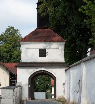 Zdjęcie nr 70: Kościół jest usytuowany w centrum wsi Rudawa, na północ od głównej drogi z Zabierzowa do Chrzanowa. Teren wokół niego jest otoczony wysokim, kamiennym murem z nieregularnych ciosów kamienia, oszkarpowanym, tynkowanym, z wyjątkiem zewnętrznej części muru na zachód od południowej bramki. W murze znajdują się trzy wejścia, od wschodu, południa i zachodu. W części wschodniej muru znajduje się trójosiowa brama wjazdowa, zwieńczona łukiem wklęsło-wypukłym, z trzema przelotami: środkowym wyższym i szerszym, zamkniętym łukiem odcinkowym i bocznymi węższymi i niższymi, zamkniętymi łukiem półkolistym (północne zamurowane). Część środkowa jest flankowana zdwojonymi pilastrami, podtrzymującymi profilowane uskokowe belkowanie z przyczółkiem o profilowanym łuku falistym, zwieńczonym równoramiennym krzyżem. W przyczółku wnęka z figurą św. Floriana. Bramki od strony zachodniej i południowej prostokątne, z przejściem zakończonym płaskim łukiem odcinkowym, z profilowanym gzymsem, zwieńczonym trójkątnym przyczółkiem. Przejścia zamykane drewnianymi ażurowymi i pomalowanymi na ciemnobrązowo jednoskrzydłowymi drzwiami. Poprzez bramkę od zachodu zejście kamiennymi schodami poprowadzonymi wzdłuż muru na dziedziniec plebański, usytuowany poniżej terenu kościelnego. 
W północno-wschodnim narożniku muru niewielka murowana i tynkowana kostnica na planie kwadratu, nakryta dachem namiotowym, łamanym, zakończonym ośmioboczną ślepą latarnią.

Po stronie południowej, poniżej placu kościelnego, do muru przylega murowana, tynkowana, prostokątna i dwukondygnacyjna „zegarowa” wieża bramna nakryta namiotowym dachem z wysoką drewnianą ośmioboczną latarnią o cebulastym hełmie. W wieży znajduje się przejazd wiodący na dziedziniec plebański, z sienią otwartą na przestrzał w dolnej kondygnacji i z lamusem dostępnym od strony placu kościelnego w górnej. 

W południowej części muru, w pobliżu południowo-wschodniego narożnika placu kościelnego, nadbudowana kamienna dzwonnica parawanowa z zawieszonymi czterema dzwonami.  

We wschodniej części placu kościelnego pomiędzy bramką wschodnią a kostnicą znajduje się kamienna ambona, o ośmiobocznej podstawie przechodzącej w szerszy, również ośmioboczny korpus, zakończony kamiennym parapetem, z kamiennymi schodami prowadzącymi na ambonę od strony wschodniej. 

Kościół jest orientowany, prawie w całości zbudowany z cegły, otynkowany z wyjątkiem prezbiterium. Wnętrze kościoła tworzy niewielkie, prostokątne, jednoprzęsłowe prezbiterium zakończone prostą ścianą i nakryte pozornym sklepieniem krzyżowo-żebrowym. Nawa jest szersza, prawie kwadratowa, nakryta drewnianym stropem. Prezbiterium z nawą są połączone szeroką, ostrołukową arkadą w ścianie tęczowej. Od północy do prezbiterium przylega założona na planie prostokąta dwuprzęsłowa zakrystia, nakryta sklepieniem krzyżowym. Wejście do zakrystii zaznaczone gotyckim, kamiennym, sfazowanym portalem zamkniętym łukiem ostrym. Od zachodu do zakrystii przylega niewielkie pomieszczenie gospodarcze, do którego z zakrystii prowadzą ostrołukowe drzwi. Zakrystia oświetlona ostrołukowym oknem w ścianie wschodniej, wypełnionym witrażem z tafelek w kształcie sześciokąta foremnego, ze szkła surowego, tzw. katedralnego. 

Od południa do nawy przylega kaplica o formach renesansowych, dwukondygnacyjna, założona na planie kwadratu. W dolnej kondygnacji sklepiona krzyżowo-żebrowo kruchta otwarta do nawy szeroką, zamkniętą półkoliście arkadą.

Ponad kruchtą kaplica św. Kazimierza, nakryta wspartą na pendentywach kopułą z latarnią. Z kruchty do kaplicy prowadzą kręte kamienne schody umieszczone od zachodu w półkolistej wieżyczce. Prostokątne wejście z krypty na klatkę schodową ujęte kamiennym profilowanym portalem. Kaplica otwarta do nawy szeroką, zamkniętą półkoliście arkadą, o kształcie i wymiarach analogicznych do arkady znajdującej się poniżej. Kaplicę, prócz latarni, oświetla prostokątne okno w ścianie południowej, wypełnione witrażem z tafelek w kształcie gomółek, ze szkła surowego, tzw. katedralnego. Na zachodniej ścianie nawy chór muzyczny, dostępny klatką schodową ukrytą w zewnętrznym aneksie przylegającym do zachodniej elewacji nawy i południowej elewacji wieży-dzwonnicy. 

Nawę i prezbiterium oświetlają umieszczone w południowych ścianach prostokątne, rozglifione okna: jedno w prezbiterium, dwa w nawie. Wszystkie wypełnione witrażami z tafelek w kształcie gomółek, ze szkła surowego, tzw. katedralnego. 

Do kościoła prowadzą dwa wejścia: poprzez arkadę z kruchty południowej oraz szerokie wejście główne prostokątne, zamknięte łukiem odcinkowym, prowadzące do kościoła z obszernej kruchty od strony zachodniej, znajdującej się w murowanym przyziemiu wieży - dzwonnicy. Kruchta, założona na planie kwadratu i nakryta murowanym stropem, doświetlona jest dwoma prostokątnymi oknami umieszczonymi naprzeciw siebie w ścianach północnej i południowej.
 
W zewnętrznej elewacji kościoła widoczny niewysoki kamienny cokół wykonany z nieregularnych ciosów kamienia. Prezbiterium, niższe od nawy, murowane z cegły w układzie wedyjskim, z domieszką układu polskiego. Wschodnie naroża prezbiterium zaakcentowane płaskimi lizenami. We wschodniej ścianie widoczny zarys zamurowanego wydłużonego okna zamkniętego lekko zaostrzonym łukiem, w trójkątnym szczycie znajduje się niewielkie wąskie okienko zakończone łukiem półkolistym. Południowa ściana prezbiterium ozdobiona fryzem z cegieł. Do ściany północnej prezbiterium przylega zakrystia, oszkarpowana, nakryta dachem pulpitowym, z dobudowanym od niej niewielkim aneksem, nakrytym takim samym zadaszeniem. Do wschodniej ściany prezbiterium przylega ogrójec nakryty dachem namiotowym z cebulastym zwieńczeniem, wspartym na sześciu smukłych, profilowanych drewnianych słupach z mieczami, pomiędzy którymi od północy i południa ażurowa drewniana balustrada. 

Nawa oszkarpowana w narożnikach. Elewacje bez podziałów architektonicznych. Od strony południowej do nawy dobudowana dwukondygnacyjna kaplica nakryta kopułą z latarnią, podzielona na dwie kondygnacje. W dolnej kondygnacji od południa wejście do kruchty zaznaczone kamiennym portalem o sfazowanych węgarach i lekko zaostrzonym łuku. Wejście zamykają drewniane dwuskrzydłowe drzwi ozdobione kratownicą z żelaznych listew. Od zachodu do kaplicy przylega półokrągła wieżyczka nakryta daszkiem stożkowym. 

Do zachodniej fasady kościoła dostawiona niska, założona na planie kwadratu trójkondygnacyjna wieża-dzwonnica: w dolnej części murowana, w narożach wzmocniona kamiennymi szkarpami, w górnej drewniana konstrukcji słupowo-ramowej z nadwieszoną izbicą i nakryta dachem półszczytowym. W dolnej, murowanej kondygnacji, na osi kościoła, prostokątne wejście do kruchty zaakcentowane przedsionkiem w kształcie ostrołukowej arkady i czterostopniowymi schodami. Przedsionek nakryty dachem dwuspadowym. Do zachodniej elewacji nawy i południowej elewacji dzwonnicy przylega niewielki, wysoki drewniany aneks, nakryty dachem pulpitowym, mieszczący klatkę schodową prowadzącą na górną kondygnację dzwonnicy i na chór muzyczny w nawie kościoła. Prostokątne wejście w południowej ścianie aneksu, do którego prowadzą pięciostopniowe proste schody. Ponad nimi, na wysokości drugiej kondygnacji dzwonnicy, niewielkie kwadratowe okno. 

Prezbiterium i nawa przykryte stromymi dachami dwuspadowymi, zamkniętymi od wschodu i zachodu szczytami sterczynowymi. Wieżyczka na sygnaturkę ośmioboczna, w dolnej części barokowa, w górnej części nowsza.