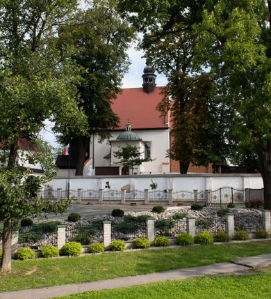 Zdjęcie nr 69: Kościół jest usytuowany w centrum wsi Rudawa, na północ od głównej drogi z Zabierzowa do Chrzanowa. Teren wokół niego jest otoczony wysokim, kamiennym murem z nieregularnych ciosów kamienia, oszkarpowanym, tynkowanym, z wyjątkiem zewnętrznej części muru na zachód od południowej bramki. W murze znajdują się trzy wejścia, od wschodu, południa i zachodu. W części wschodniej muru znajduje się trójosiowa brama wjazdowa, zwieńczona łukiem wklęsło-wypukłym, z trzema przelotami: środkowym wyższym i szerszym, zamkniętym łukiem odcinkowym i bocznymi węższymi i niższymi, zamkniętymi łukiem półkolistym (północne zamurowane). Część środkowa jest flankowana zdwojonymi pilastrami, podtrzymującymi profilowane uskokowe belkowanie z przyczółkiem o profilowanym łuku falistym, zwieńczonym równoramiennym krzyżem. W przyczółku wnęka z figurą św. Floriana. Bramki od strony zachodniej i południowej prostokątne, z przejściem zakończonym płaskim łukiem odcinkowym, z profilowanym gzymsem, zwieńczonym trójkątnym przyczółkiem. Przejścia zamykane drewnianymi ażurowymi i pomalowanymi na ciemnobrązowo jednoskrzydłowymi drzwiami. Poprzez bramkę od zachodu zejście kamiennymi schodami poprowadzonymi wzdłuż muru na dziedziniec plebański, usytuowany poniżej terenu kościelnego. 
W północno-wschodnim narożniku muru niewielka murowana i tynkowana kostnica na planie kwadratu, nakryta dachem namiotowym, łamanym, zakończonym ośmioboczną ślepą latarnią.

Po stronie południowej, poniżej placu kościelnego, do muru przylega murowana, tynkowana, prostokątna i dwukondygnacyjna „zegarowa” wieża bramna nakryta namiotowym dachem z wysoką drewnianą ośmioboczną latarnią o cebulastym hełmie. W wieży znajduje się przejazd wiodący na dziedziniec plebański, z sienią otwartą na przestrzał w dolnej kondygnacji i z lamusem dostępnym od strony placu kościelnego w górnej. 

W południowej części muru, w pobliżu południowo-wschodniego narożnika placu kościelnego, nadbudowana kamienna dzwonnica parawanowa z zawieszonymi czterema dzwonami.  

We wschodniej części placu kościelnego pomiędzy bramką wschodnią a kostnicą znajduje się kamienna ambona, o ośmiobocznej podstawie przechodzącej w szerszy, również ośmioboczny korpus, zakończony kamiennym parapetem, z kamiennymi schodami prowadzącymi na ambonę od strony wschodniej. 

Kościół jest orientowany, prawie w całości zbudowany z cegły, otynkowany z wyjątkiem prezbiterium. Wnętrze kościoła tworzy niewielkie, prostokątne, jednoprzęsłowe prezbiterium zakończone prostą ścianą i nakryte pozornym sklepieniem krzyżowo-żebrowym. Nawa jest szersza, prawie kwadratowa, nakryta drewnianym stropem. Prezbiterium z nawą są połączone szeroką, ostrołukową arkadą w ścianie tęczowej. Od północy do prezbiterium przylega założona na planie prostokąta dwuprzęsłowa zakrystia, nakryta sklepieniem krzyżowym. Wejście do zakrystii zaznaczone gotyckim, kamiennym, sfazowanym portalem zamkniętym łukiem ostrym. Od zachodu do zakrystii przylega niewielkie pomieszczenie gospodarcze, do którego z zakrystii prowadzą ostrołukowe drzwi. Zakrystia oświetlona ostrołukowym oknem w ścianie wschodniej, wypełnionym witrażem z tafelek w kształcie sześciokąta foremnego, ze szkła surowego, tzw. katedralnego. 

Od południa do nawy przylega kaplica o formach renesansowych, dwukondygnacyjna, założona na planie kwadratu. W dolnej kondygnacji sklepiona krzyżowo-żebrowo kruchta otwarta do nawy szeroką, zamkniętą półkoliście arkadą.

Ponad kruchtą kaplica św. Kazimierza, nakryta wspartą na pendentywach kopułą z latarnią. Z kruchty do kaplicy prowadzą kręte kamienne schody umieszczone od zachodu w półkolistej wieżyczce. Prostokątne wejście z krypty na klatkę schodową ujęte kamiennym profilowanym portalem. Kaplica otwarta do nawy szeroką, zamkniętą półkoliście arkadą, o kształcie i wymiarach analogicznych do arkady znajdującej się poniżej. Kaplicę, prócz latarni, oświetla prostokątne okno w ścianie południowej, wypełnione witrażem z tafelek w kształcie gomółek, ze szkła surowego, tzw. katedralnego. Na zachodniej ścianie nawy chór muzyczny, dostępny klatką schodową ukrytą w zewnętrznym aneksie przylegającym do zachodniej elewacji nawy i południowej elewacji wieży-dzwonnicy. 

Nawę i prezbiterium oświetlają umieszczone w południowych ścianach prostokątne, rozglifione okna: jedno w prezbiterium, dwa w nawie. Wszystkie wypełnione witrażami z tafelek w kształcie gomółek, ze szkła surowego, tzw. katedralnego. 

Do kościoła prowadzą dwa wejścia: poprzez arkadę z kruchty południowej oraz szerokie wejście główne prostokątne, zamknięte łukiem odcinkowym, prowadzące do kościoła z obszernej kruchty od strony zachodniej, znajdującej się w murowanym przyziemiu wieży - dzwonnicy. Kruchta, założona na planie kwadratu i nakryta murowanym stropem, doświetlona jest dwoma prostokątnymi oknami umieszczonymi naprzeciw siebie w ścianach północnej i południowej.
 
W zewnętrznej elewacji kościoła widoczny niewysoki kamienny cokół wykonany z nieregularnych ciosów kamienia. Prezbiterium, niższe od nawy, murowane z cegły w układzie wedyjskim, z domieszką układu polskiego. Wschodnie naroża prezbiterium zaakcentowane płaskimi lizenami. We wschodniej ścianie widoczny zarys zamurowanego wydłużonego okna zamkniętego lekko zaostrzonym łukiem, w trójkątnym szczycie znajduje się niewielkie wąskie okienko zakończone łukiem półkolistym. Południowa ściana prezbiterium ozdobiona fryzem z cegieł. Do ściany północnej prezbiterium przylega zakrystia, oszkarpowana, nakryta dachem pulpitowym, z dobudowanym od niej niewielkim aneksem, nakrytym takim samym zadaszeniem. Do wschodniej ściany prezbiterium przylega ogrójec nakryty dachem namiotowym z cebulastym zwieńczeniem, wspartym na sześciu smukłych, profilowanych drewnianych słupach z mieczami, pomiędzy którymi od północy i południa ażurowa drewniana balustrada. 

Nawa oszkarpowana w narożnikach. Elewacje bez podziałów architektonicznych. Od strony południowej do nawy dobudowana dwukondygnacyjna kaplica nakryta kopułą z latarnią, podzielona na dwie kondygnacje. W dolnej kondygnacji od południa wejście do kruchty zaznaczone kamiennym portalem o sfazowanych węgarach i lekko zaostrzonym łuku. Wejście zamykają drewniane dwuskrzydłowe drzwi ozdobione kratownicą z żelaznych listew. Od zachodu do kaplicy przylega półokrągła wieżyczka nakryta daszkiem stożkowym. 

Do zachodniej fasady kościoła dostawiona niska, założona na planie kwadratu trójkondygnacyjna wieża-dzwonnica: w dolnej części murowana, w narożach wzmocniona kamiennymi szkarpami, w górnej drewniana konstrukcji słupowo-ramowej z nadwieszoną izbicą i nakryta dachem półszczytowym. W dolnej, murowanej kondygnacji, na osi kościoła, prostokątne wejście do kruchty zaakcentowane przedsionkiem w kształcie ostrołukowej arkady i czterostopniowymi schodami. Przedsionek nakryty dachem dwuspadowym. Do zachodniej elewacji nawy i południowej elewacji dzwonnicy przylega niewielki, wysoki drewniany aneks, nakryty dachem pulpitowym, mieszczący klatkę schodową prowadzącą na górną kondygnację dzwonnicy i na chór muzyczny w nawie kościoła. Prostokątne wejście w południowej ścianie aneksu, do którego prowadzą pięciostopniowe proste schody. Ponad nimi, na wysokości drugiej kondygnacji dzwonnicy, niewielkie kwadratowe okno. 

Prezbiterium i nawa przykryte stromymi dachami dwuspadowymi, zamkniętymi od wschodu i zachodu szczytami sterczynowymi. Wieżyczka na sygnaturkę ośmioboczna, w dolnej części barokowa, w górnej części nowsza.