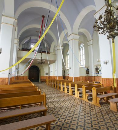 Zdjęcie nr 25: Kościół orientowany, murowany, trójnawowy, czteroprzęsłowy, z jednoprzęsłowym prezbiterium zakończonym wielobocznie. Do prezbiterium dostawione symetrycznie aneksy, od zachodu kruchta, w przyziemiu wieża flankowana dwiema klatkami schodowymi (pomieszczeniem gospodarczym?). Nawy oddzielone od siebie masywnymi filarami opilastrowanymi, z uproszczonymi kapitelami, podtrzymującymi arkady. Nawy i prezbiterium nakryte sklepieniem krzyżowym na gurtach, pięcioboczne zamknięcie prezbiterium sklepieniem parasolowatym. Nawę i prezbiterium oświetlają wysokie, prostokątne okna zakończone półkoliście z oknami trójrzędowymi dwuosiowymi, zakończonymi maswerkami. Układ komunikacyjny zaznaczony kamiennymi portalami o sfazowanych węgarach. Do kościoła prowadzą duże prostokątne drzwi, w kruchcie zakończone półkoliście. Tam też prostokątne wejścia do aneksów bocznych. W południowo-zachodniej ścianie prostokątne wejście zamknięte ściętym łukiem nadwieszonym. Takie samo wejście do aneksu południowego przy prezbiterium. Do aneksu północnego przy prezbiterium prostokątne wejście zamknięte łukiem odcinkowym, ujęte kamiennym portalem, zamkniętym półkoliście. Wejście w ścianie nawy południowej zaznaczone kamiennym portalem zamkniętym łukiem ostrym. W skrajnym przęśle nawy od zachodu chór muzyczny wsparty na dwóch filarach międzynawowych. W części chóru nad kruchtą wnęka otwarta kamienną rozetą. Fasada kościoła trójosiowa, dwukondygnacyjna, ujęta szkarpami z uskokami. Szkarpy z uskokami wydzielają także środkową oś fasady. W jej dolnej kondygnacji znajduje się kamienny portal główny, ujęty uskokowo ustawionymi półkolumnami i zakończony półkolistym tympanonem wypełnionym płaskorzeźbą ze sceną Zesłania Ducha Świętego. Powyżej wypełniona maswerkiem rozeta w profilowanej ramie. Między nią a biforium niewielki herb rodziny Potockich. Szczyt dekoruje fryz arkadkowy. W osiach bocznych wysokie, dwudzielne okna z maswerkiem. Budynek ustawiony na kamiennym cokole, oszkarpowany, z kamiennymi detalami, dekorowany fryzem arkadkowym, z otwartym od zewnątrz obejściem prezbiterium. W obejściu płaskorzeźbiona grupa Ukrzyżowania. Dachy kryte blachą – nawy i wieży dwuspadowe, przybudówek przy prezbiterium pulpitowe, nad obejściem i prezbiterium wieloboczne. Na kalenicy wieżyczka na sygnaturkę z latarnią i wielobocznym dachem. 