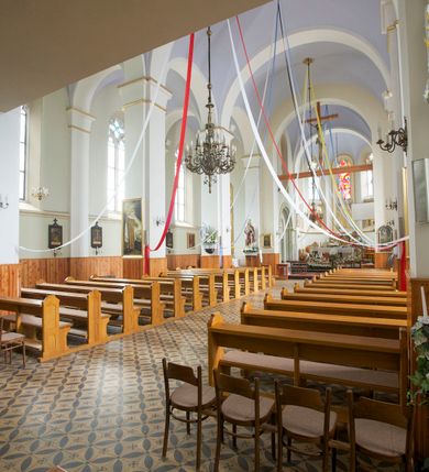 Zdjęcie nr 33: Kościół orientowany, murowany, trójnawowy, czteroprzęsłowy, z jednoprzęsłowym prezbiterium zakończonym wielobocznie. Do prezbiterium dostawione symetrycznie aneksy, od zachodu kruchta, w przyziemiu wieża flankowana dwiema klatkami schodowymi (pomieszczeniem gospodarczym?). Nawy oddzielone od siebie masywnymi filarami opilastrowanymi, z uproszczonymi kapitelami, podtrzymującymi arkady. Nawy i prezbiterium nakryte sklepieniem krzyżowym na gurtach, pięcioboczne zamknięcie prezbiterium sklepieniem parasolowatym. Nawę i prezbiterium oświetlają wysokie, prostokątne okna zakończone półkoliście z oknami trójrzędowymi dwuosiowymi, zakończonymi maswerkami. Układ komunikacyjny zaznaczony kamiennymi portalami o sfazowanych węgarach. Do kościoła prowadzą duże prostokątne drzwi, w kruchcie zakończone półkoliście. Tam też prostokątne wejścia do aneksów bocznych. W południowo-zachodniej ścianie prostokątne wejście zamknięte ściętym łukiem nadwieszonym. Takie samo wejście do aneksu południowego przy prezbiterium. Do aneksu północnego przy prezbiterium prostokątne wejście zamknięte łukiem odcinkowym, ujęte kamiennym portalem, zamkniętym półkoliście. Wejście w ścianie nawy południowej zaznaczone kamiennym portalem zamkniętym łukiem ostrym. W skrajnym przęśle nawy od zachodu chór muzyczny wsparty na dwóch filarach międzynawowych. W części chóru nad kruchtą wnęka otwarta kamienną rozetą. Fasada kościoła trójosiowa, dwukondygnacyjna, ujęta szkarpami z uskokami. Szkarpy z uskokami wydzielają także środkową oś fasady. W jej dolnej kondygnacji znajduje się kamienny portal główny, ujęty uskokowo ustawionymi półkolumnami i zakończony półkolistym tympanonem wypełnionym płaskorzeźbą ze sceną Zesłania Ducha Świętego. Powyżej wypełniona maswerkiem rozeta w profilowanej ramie. Między nią a biforium niewielki herb rodziny Potockich. Szczyt dekoruje fryz arkadkowy. W osiach bocznych wysokie, dwudzielne okna z maswerkiem. Budynek ustawiony na kamiennym cokole, oszkarpowany, z kamiennymi detalami, dekorowany fryzem arkadkowym, z otwartym od zewnątrz obejściem prezbiterium. W obejściu płaskorzeźbiona grupa Ukrzyżowania. Dachy kryte blachą – nawy i wieży dwuspadowe, przybudówek przy prezbiterium pulpitowe, nad obejściem i prezbiterium wieloboczne. Na kalenicy wieżyczka na sygnaturkę z latarnią i wielobocznym dachem. 
