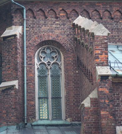 Zdjęcie nr 17: Kościół orientowany, murowany, trójnawowy, czteroprzęsłowy, z jednoprzęsłowym prezbiterium zakończonym wielobocznie. Do prezbiterium dostawione symetrycznie aneksy, od zachodu kruchta, w przyziemiu wieża flankowana dwiema klatkami schodowymi (pomieszczeniem gospodarczym?). Nawy oddzielone od siebie masywnymi filarami opilastrowanymi, z uproszczonymi kapitelami, podtrzymującymi arkady. Nawy i prezbiterium nakryte sklepieniem krzyżowym na gurtach, pięcioboczne zamknięcie prezbiterium sklepieniem parasolowatym. Nawę i prezbiterium oświetlają wysokie, prostokątne okna zakończone półkoliście z oknami trójrzędowymi dwuosiowymi, zakończonymi maswerkami. Układ komunikacyjny zaznaczony kamiennymi portalami o sfazowanych węgarach. Do kościoła prowadzą duże prostokątne drzwi, w kruchcie zakończone półkoliście. Tam też prostokątne wejścia do aneksów bocznych. W południowo-zachodniej ścianie prostokątne wejście zamknięte ściętym łukiem nadwieszonym. Takie samo wejście do aneksu południowego przy prezbiterium. Do aneksu północnego przy prezbiterium prostokątne wejście zamknięte łukiem odcinkowym, ujęte kamiennym portalem, zamkniętym półkoliście. Wejście w ścianie nawy południowej zaznaczone kamiennym portalem zamkniętym łukiem ostrym. W skrajnym przęśle nawy od zachodu chór muzyczny wsparty na dwóch filarach międzynawowych. W części chóru nad kruchtą wnęka otwarta kamienną rozetą. Fasada kościoła trójosiowa, dwukondygnacyjna, ujęta szkarpami z uskokami. Szkarpy z uskokami wydzielają także środkową oś fasady. W jej dolnej kondygnacji znajduje się kamienny portal główny, ujęty uskokowo ustawionymi półkolumnami i zakończony półkolistym tympanonem wypełnionym płaskorzeźbą ze sceną Zesłania Ducha Świętego. Powyżej wypełniona maswerkiem rozeta w profilowanej ramie. Między nią a biforium niewielki herb rodziny Potockich. Szczyt dekoruje fryz arkadkowy. W osiach bocznych wysokie, dwudzielne okna z maswerkiem. Budynek ustawiony na kamiennym cokole, oszkarpowany, z kamiennymi detalami, dekorowany fryzem arkadkowym, z otwartym od zewnątrz obejściem prezbiterium. W obejściu płaskorzeźbiona grupa Ukrzyżowania. Dachy kryte blachą – nawy i wieży dwuspadowe, przybudówek przy prezbiterium pulpitowe, nad obejściem i prezbiterium wieloboczne. Na kalenicy wieżyczka na sygnaturkę z latarnią i wielobocznym dachem. 