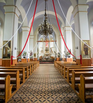 Zdjęcie nr 34: Kościół orientowany, murowany, trójnawowy, czteroprzęsłowy, z jednoprzęsłowym prezbiterium zakończonym wielobocznie. Do prezbiterium dostawione symetrycznie aneksy, od zachodu kruchta, w przyziemiu wieża flankowana dwiema klatkami schodowymi (pomieszczeniem gospodarczym?). Nawy oddzielone od siebie masywnymi filarami opilastrowanymi, z uproszczonymi kapitelami, podtrzymującymi arkady. Nawy i prezbiterium nakryte sklepieniem krzyżowym na gurtach, pięcioboczne zamknięcie prezbiterium sklepieniem parasolowatym. Nawę i prezbiterium oświetlają wysokie, prostokątne okna zakończone półkoliście z oknami trójrzędowymi dwuosiowymi, zakończonymi maswerkami. Układ komunikacyjny zaznaczony kamiennymi portalami o sfazowanych węgarach. Do kościoła prowadzą duże prostokątne drzwi, w kruchcie zakończone półkoliście. Tam też prostokątne wejścia do aneksów bocznych. W południowo-zachodniej ścianie prostokątne wejście zamknięte ściętym łukiem nadwieszonym. Takie samo wejście do aneksu południowego przy prezbiterium. Do aneksu północnego przy prezbiterium prostokątne wejście zamknięte łukiem odcinkowym, ujęte kamiennym portalem, zamkniętym półkoliście. Wejście w ścianie nawy południowej zaznaczone kamiennym portalem zamkniętym łukiem ostrym. W skrajnym przęśle nawy od zachodu chór muzyczny wsparty na dwóch filarach międzynawowych. W części chóru nad kruchtą wnęka otwarta kamienną rozetą. Fasada kościoła trójosiowa, dwukondygnacyjna, ujęta szkarpami z uskokami. Szkarpy z uskokami wydzielają także środkową oś fasady. W jej dolnej kondygnacji znajduje się kamienny portal główny, ujęty uskokowo ustawionymi półkolumnami i zakończony półkolistym tympanonem wypełnionym płaskorzeźbą ze sceną Zesłania Ducha Świętego. Powyżej wypełniona maswerkiem rozeta w profilowanej ramie. Między nią a biforium niewielki herb rodziny Potockich. Szczyt dekoruje fryz arkadkowy. W osiach bocznych wysokie, dwudzielne okna z maswerkiem. Budynek ustawiony na kamiennym cokole, oszkarpowany, z kamiennymi detalami, dekorowany fryzem arkadkowym, z otwartym od zewnątrz obejściem prezbiterium. W obejściu płaskorzeźbiona grupa Ukrzyżowania. Dachy kryte blachą – nawy i wieży dwuspadowe, przybudówek przy prezbiterium pulpitowe, nad obejściem i prezbiterium wieloboczne. Na kalenicy wieżyczka na sygnaturkę z latarnią i wielobocznym dachem. 