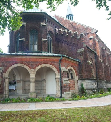 Zdjęcie nr 8: Kościół orientowany, murowany, trójnawowy, czteroprzęsłowy, z jednoprzęsłowym prezbiterium zakończonym wielobocznie. Do prezbiterium dostawione symetrycznie aneksy, od zachodu kruchta, w przyziemiu wieża flankowana dwiema klatkami schodowymi (pomieszczeniem gospodarczym?). Nawy oddzielone od siebie masywnymi filarami opilastrowanymi, z uproszczonymi kapitelami, podtrzymującymi arkady. Nawy i prezbiterium nakryte sklepieniem krzyżowym na gurtach, pięcioboczne zamknięcie prezbiterium sklepieniem parasolowatym. Nawę i prezbiterium oświetlają wysokie, prostokątne okna zakończone półkoliście z oknami trójrzędowymi dwuosiowymi, zakończonymi maswerkami. Układ komunikacyjny zaznaczony kamiennymi portalami o sfazowanych węgarach. Do kościoła prowadzą duże prostokątne drzwi, w kruchcie zakończone półkoliście. Tam też prostokątne wejścia do aneksów bocznych. W południowo-zachodniej ścianie prostokątne wejście zamknięte ściętym łukiem nadwieszonym. Takie samo wejście do aneksu południowego przy prezbiterium. Do aneksu północnego przy prezbiterium prostokątne wejście zamknięte łukiem odcinkowym, ujęte kamiennym portalem, zamkniętym półkoliście. Wejście w ścianie nawy południowej zaznaczone kamiennym portalem zamkniętym łukiem ostrym. W skrajnym przęśle nawy od zachodu chór muzyczny wsparty na dwóch filarach międzynawowych. W części chóru nad kruchtą wnęka otwarta kamienną rozetą. Fasada kościoła trójosiowa, dwukondygnacyjna, ujęta szkarpami z uskokami. Szkarpy z uskokami wydzielają także środkową oś fasady. W jej dolnej kondygnacji znajduje się kamienny portal główny, ujęty uskokowo ustawionymi półkolumnami i zakończony półkolistym tympanonem wypełnionym płaskorzeźbą ze sceną Zesłania Ducha Świętego. Powyżej wypełniona maswerkiem rozeta w profilowanej ramie. Między nią a biforium niewielki herb rodziny Potockich. Szczyt dekoruje fryz arkadkowy. W osiach bocznych wysokie, dwudzielne okna z maswerkiem. Budynek ustawiony na kamiennym cokole, oszkarpowany, z kamiennymi detalami, dekorowany fryzem arkadkowym, z otwartym od zewnątrz obejściem prezbiterium. W obejściu płaskorzeźbiona grupa Ukrzyżowania. Dachy kryte blachą – nawy i wieży dwuspadowe, przybudówek przy prezbiterium pulpitowe, nad obejściem i prezbiterium wieloboczne. Na kalenicy wieżyczka na sygnaturkę z latarnią i wielobocznym dachem. 