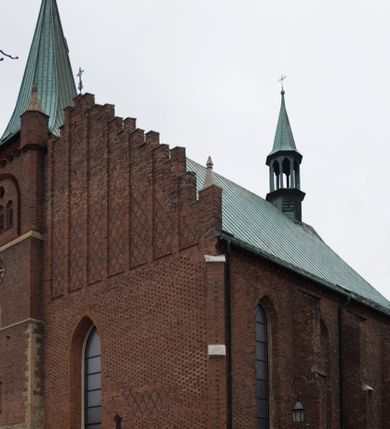 Zdjęcie nr 1: Kościół położony na obszernym placu przylegającym do wschodniej pierzei rynku, na północ od zamku. Plac otoczony ceglanym murem z filarkami. Przed kościołem wydzielony plac, dawny cmentarz, na nim figura św. Jana Kantego. W południowo-wschodnim narożu placu grobowiec księżnej Apolonii Potockiej. Kościół orientowany, halowy, trójnawowy, czteroprzęsłowy, z dwuprzęsłowym zamkniętym wielobocznie prezbiterium. Nawa główna szersza od naw bocznych. Nawy boczne zakończone od wschodu poligonalnymi kaplicami. Od strony północnej do nawy przylega kruchta. W północno-zachodnim narożniku kwadratowa wieża mieszcząca kaplicę w przyziemiu. Do zachodniego przęsła nawy głównej dostawiony głęboki ryzalit z kruchtą w przyziemiu i chórem na piętrze z prospektem organowym. Od północnej strony przylega piętrowa zakrystia, zamknięta wielobocznie. Nawa główna od bocznych oddzielona czworobocznymi filarami o ściętych narożach. Prezbiterium otwarte do korpusu ostrołukową tęczą. W korpusie sklepienie o konstrukcji żelbetowej, stylizowane na gotyckie. W kaplicy pod wieżą sklepienie kolebkowe, w kruchcie zachodniej sufit. Prezbiterium nakryte sklepieniem krzyżowo-żebrowym z żebrami spływającymi na konsole. Wnętrze oświetlają okna ostrołukowe, wypełnione witrażami; dwa w zamknięciu prezbiterium (środkowy otwór zamurowany), dwa na ścianie południowej. Portal z prezbiterium do zakrystii zamknięty łukiem w ośli grzbiet. Otwory drzwiowe prostokątne, różnej wielkości. Kaplica pod wieżą otwarta do wnętrza ostrołukowymi arkadami. Otwory okienne wąskie, prostokątne, ostrołukowe, wypełnione witrażem; cztery w ścianie północnej i południowej, jedno, szersze w ścianie zachodniej nad chórem. Wieża oświetlona małymi, wąskimi oknami zakończonymi łukiem odcinkowym i ostrołukowym. Fasada jednoosiowa, dwukondygnacyjna, zwieńczona szczytem schodkowym z ceglanymi laskami. Niesymetrycznie umieszczone wejście ujęte kamiennym, profilowanym portalem, zamkniętym ostrołukowo. Ponad nim rozglifione ostrołukowe okno. Od północy wieża wbudowana w naroże kościoła, wysunięta nieco przed lico fasady. W dolnej partii kamienna, w górnej ceglana, na rzucie prostokąta, czterokondygnacyjna. Piętro pierwsze i drugie oddzielone kamiennym gzymsem. Trzy dolne kondygnacje gotyckie, czwarta neogotycka (projektu Franciszka Marii Lanciego z 1836 r). Na osi pojedyncze okna. W parterze okno ciosowe, prostokątne, ponad nim wmurowany późnogotycki maswerk ostrołukowy z motywami rybich pęcherzy i psiego zęba, wyżej kartusz z herbem Leliwa. Na pierwszym piętrze okno ostrołukowe z parapetem na konsolkach, w opasce ceglanej zamkniętej ostrołukiem wklęsłym. Drugie piętro, okno ostrołukowe w opasce kamiennej, ponad nim okrągła tarcza zegarowa. Ostatnia kondygnacja ze ściętymi narożami, na których wysunięte przed lico muru krenelażowe wieżyczki zwieńczone kamiennymi szczytami w formie ostrosłupów. Od zachodu masywny łuk półokrągły uformowany z kształtek ceramicznych, w jego polu triforium ostrołukowe. Ponad nim okulus. Pod okapem dachu fryz z ceglanych konsolek oraz gąsiory układane w motyw rybiej łuski. Dach iglicowy. Elewacja południowa. Portal kamienny na cokole, profilowany, ostrołukowy. Archiwolty przechodzące w łuk o formie oślego grzbietu, wsparte na konsolkach zdobionych motywem roślinnym. Skrajna archiwolta z czołgankami zwieńczona pinaklem z kwiatonem. Po bokach analogiczne pinakle; W prezbiterium portal kamienny na cokole, profilowany, ostrołukowy, z dekoracją z motywem skręconego sznura; w kluczu herb Odrowąż, oraz data 1767 i litery LG OH OFP. W ścianę korpusu wmurowane kamienne epitafium ks. Pawła Gabańskiego plebana zatorskiego (zm. 1825), nad nim kartusz z herbem Łodzia.Trzy okna analogiczne jak w fasadzie, i jedno o połowę węższe. Elewacja północna. Kruchta ceglana, na cokole, opięta przyporami. Na osi portal kamienny, profilowany, ostrołukowy. Ponad nim kamienna rozeta z monogramem Marii, po bokach dwa okna o wykroju czworoliścia w okrągłych, kamiennych opaskach. Od strony północno-zachodniej zakrystia na rzucie prostokąta, zamknięta wielobocznie, piętrowa, w dolnej części kamienna (pozostałość pierwotnego kościoła), wyżej ceglana (piętro dobudowane 1915 r.). Od północy portal w opasce ceglanej, zamknięty łukiem odcinkowym. Ponad nim ostrołukowe, ceglane okno. Dwa okna analogiczne jak w fasadzie i jedno o połowę węższe. Kościół opięty przyporami, na wysokości ław okiennych gzyms kapnikowy wyłamany nad portalem północnym. Przypory z kapnikami w zwieńczeniu i na 2/3 wysokości. Pod dachem gzyms konsolkowy. Dach dwuspadowy, sygnaturka wieloboczna z ostrołukowymi prześwitami, zwieńczona hełmem iglicowym.