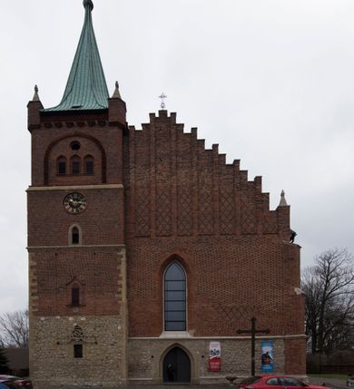 Zdjęcie nr 2: Kościół położony na obszernym placu przylegającym do wschodniej pierzei rynku, na północ od zamku. Plac otoczony ceglanym murem z filarkami. Przed kościołem wydzielony plac, dawny cmentarz, na nim figura św. Jana Kantego. W południowo-wschodnim narożu placu grobowiec księżnej Apolonii Potockiej. Kościół orientowany, halowy, trójnawowy, czteroprzęsłowy, z dwuprzęsłowym zamkniętym wielobocznie prezbiterium. Nawa główna szersza od naw bocznych. Nawy boczne zakończone od wschodu poligonalnymi kaplicami. Od strony północnej do nawy przylega kruchta. W północno-zachodnim narożniku kwadratowa wieża mieszcząca kaplicę w przyziemiu. Do zachodniego przęsła nawy głównej dostawiony głęboki ryzalit z kruchtą w przyziemiu i chórem na piętrze z prospektem organowym. Od północnej strony przylega piętrowa zakrystia, zamknięta wielobocznie. Nawa główna od bocznych oddzielona czworobocznymi filarami o ściętych narożach. Prezbiterium otwarte do korpusu ostrołukową tęczą. W korpusie sklepienie o konstrukcji żelbetowej, stylizowane na gotyckie. W kaplicy pod wieżą sklepienie kolebkowe, w kruchcie zachodniej sufit. Prezbiterium nakryte sklepieniem krzyżowo-żebrowym z żebrami spływającymi na konsole. Wnętrze oświetlają okna ostrołukowe, wypełnione witrażami; dwa w zamknięciu prezbiterium (środkowy otwór zamurowany), dwa na ścianie południowej. Portal z prezbiterium do zakrystii zamknięty łukiem w ośli grzbiet. Otwory drzwiowe prostokątne, różnej wielkości. Kaplica pod wieżą otwarta do wnętrza ostrołukowymi arkadami. Otwory okienne wąskie, prostokątne, ostrołukowe, wypełnione witrażem; cztery w ścianie północnej i południowej, jedno, szersze w ścianie zachodniej nad chórem. Wieża oświetlona małymi, wąskimi oknami zakończonymi łukiem odcinkowym i ostrołukowym. Fasada jednoosiowa, dwukondygnacyjna, zwieńczona szczytem schodkowym z ceglanymi laskami. Niesymetrycznie umieszczone wejście ujęte kamiennym, profilowanym portalem, zamkniętym ostrołukowo. Ponad nim rozglifione ostrołukowe okno. Od północy wieża wbudowana w naroże kościoła, wysunięta nieco przed lico fasady. W dolnej partii kamienna, w górnej ceglana, na rzucie prostokąta, czterokondygnacyjna. Piętro pierwsze i drugie oddzielone kamiennym gzymsem. Trzy dolne kondygnacje gotyckie, czwarta neogotycka (projektu Franciszka Marii Lanciego z 1836 r). Na osi pojedyncze okna. W parterze okno ciosowe, prostokątne, ponad nim wmurowany późnogotycki maswerk ostrołukowy z motywami rybich pęcherzy i psiego zęba, wyżej kartusz z herbem Leliwa. Na pierwszym piętrze okno ostrołukowe z parapetem na konsolkach, w opasce ceglanej zamkniętej ostrołukiem wklęsłym. Drugie piętro, okno ostrołukowe w opasce kamiennej, ponad nim okrągła tarcza zegarowa. Ostatnia kondygnacja ze ściętymi narożami, na których wysunięte przed lico muru krenelażowe wieżyczki zwieńczone kamiennymi szczytami w formie ostrosłupów. Od zachodu masywny łuk półokrągły uformowany z kształtek ceramicznych, w jego polu triforium ostrołukowe. Ponad nim okulus. Pod okapem dachu fryz z ceglanych konsolek oraz gąsiory układane w motyw rybiej łuski. Dach iglicowy. Elewacja południowa. Portal kamienny na cokole, profilowany, ostrołukowy. Archiwolty przechodzące w łuk o formie oślego grzbietu, wsparte na konsolkach zdobionych motywem roślinnym. Skrajna archiwolta z czołgankami zwieńczona pinaklem z kwiatonem. Po bokach analogiczne pinakle; W prezbiterium portal kamienny na cokole, profilowany, ostrołukowy, z dekoracją z motywem skręconego sznura; w kluczu herb Odrowąż, oraz data 1767 i litery LG OH OFP. W ścianę korpusu wmurowane kamienne epitafium ks. Pawła Gabańskiego plebana zatorskiego (zm. 1825), nad nim kartusz z herbem Łodzia.Trzy okna analogiczne jak w fasadzie, i jedno o połowę węższe. Elewacja północna. Kruchta ceglana, na cokole, opięta przyporami. Na osi portal kamienny, profilowany, ostrołukowy. Ponad nim kamienna rozeta z monogramem Marii, po bokach dwa okna o wykroju czworoliścia w okrągłych, kamiennych opaskach. Od strony północno-zachodniej zakrystia na rzucie prostokąta, zamknięta wielobocznie, piętrowa, w dolnej części kamienna (pozostałość pierwotnego kościoła), wyżej ceglana (piętro dobudowane 1915 r.). Od północy portal w opasce ceglanej, zamknięty łukiem odcinkowym. Ponad nim ostrołukowe, ceglane okno. Dwa okna analogiczne jak w fasadzie i jedno o połowę węższe. Kościół opięty przyporami, na wysokości ław okiennych gzyms kapnikowy wyłamany nad portalem północnym. Przypory z kapnikami w zwieńczeniu i na 2/3 wysokości. Pod dachem gzyms konsolkowy. Dach dwuspadowy, sygnaturka wieloboczna z ostrołukowymi prześwitami, zwieńczona hełmem iglicowym.