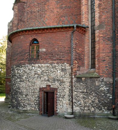 Zdjęcie nr 22: Kościół położony na obszernym placu przylegającym do wschodniej pierzei rynku, na północ od zamku. Plac otoczony ceglanym murem z filarkami. Przed kościołem wydzielony plac, dawny cmentarz, na nim figura św. Jana Kantego. W południowo-wschodnim narożu placu grobowiec księżnej Apolonii Potockiej. Kościół orientowany, halowy, trójnawowy, czteroprzęsłowy, z dwuprzęsłowym zamkniętym wielobocznie prezbiterium. Nawa główna szersza od naw bocznych. Nawy boczne zakończone od wschodu poligonalnymi kaplicami. Od strony północnej do nawy przylega kruchta. W północno-zachodnim narożniku kwadratowa wieża mieszcząca kaplicę w przyziemiu. Do zachodniego przęsła nawy głównej dostawiony głęboki ryzalit z kruchtą w przyziemiu i chórem na piętrze z prospektem organowym. Od północnej strony przylega piętrowa zakrystia, zamknięta wielobocznie. Nawa główna od bocznych oddzielona czworobocznymi filarami o ściętych narożach. Prezbiterium otwarte do korpusu ostrołukową tęczą. W korpusie sklepienie o konstrukcji żelbetowej, stylizowane na gotyckie. W kaplicy pod wieżą sklepienie kolebkowe, w kruchcie zachodniej sufit. Prezbiterium nakryte sklepieniem krzyżowo-żebrowym z żebrami spływającymi na konsole. Wnętrze oświetlają okna ostrołukowe, wypełnione witrażami; dwa w zamknięciu prezbiterium (środkowy otwór zamurowany), dwa na ścianie południowej. Portal z prezbiterium do zakrystii zamknięty łukiem w ośli grzbiet. Otwory drzwiowe prostokątne, różnej wielkości. Kaplica pod wieżą otwarta do wnętrza ostrołukowymi arkadami. Otwory okienne wąskie, prostokątne, ostrołukowe, wypełnione witrażem; cztery w ścianie północnej i południowej, jedno, szersze w ścianie zachodniej nad chórem. Wieża oświetlona małymi, wąskimi oknami zakończonymi łukiem odcinkowym i ostrołukowym. Fasada jednoosiowa, dwukondygnacyjna, zwieńczona szczytem schodkowym z ceglanymi laskami. Niesymetrycznie umieszczone wejście ujęte kamiennym, profilowanym portalem, zamkniętym ostrołukowo. Ponad nim rozglifione ostrołukowe okno. Od północy wieża wbudowana w naroże kościoła, wysunięta nieco przed lico fasady. W dolnej partii kamienna, w górnej ceglana, na rzucie prostokąta, czterokondygnacyjna. Piętro pierwsze i drugie oddzielone kamiennym gzymsem. Trzy dolne kondygnacje gotyckie, czwarta neogotycka (projektu Franciszka Marii Lanciego z 1836 r). Na osi pojedyncze okna. W parterze okno ciosowe, prostokątne, ponad nim wmurowany późnogotycki maswerk ostrołukowy z motywami rybich pęcherzy i psiego zęba, wyżej kartusz z herbem Leliwa. Na pierwszym piętrze okno ostrołukowe z parapetem na konsolkach, w opasce ceglanej zamkniętej ostrołukiem wklęsłym. Drugie piętro, okno ostrołukowe w opasce kamiennej, ponad nim okrągła tarcza zegarowa. Ostatnia kondygnacja ze ściętymi narożami, na których wysunięte przed lico muru krenelażowe wieżyczki zwieńczone kamiennymi szczytami w formie ostrosłupów. Od zachodu masywny łuk półokrągły uformowany z kształtek ceramicznych, w jego polu triforium ostrołukowe. Ponad nim okulus. Pod okapem dachu fryz z ceglanych konsolek oraz gąsiory układane w motyw rybiej łuski. Dach iglicowy. Elewacja południowa. Portal kamienny na cokole, profilowany, ostrołukowy. Archiwolty przechodzące w łuk o formie oślego grzbietu, wsparte na konsolkach zdobionych motywem roślinnym. Skrajna archiwolta z czołgankami zwieńczona pinaklem z kwiatonem. Po bokach analogiczne pinakle; W prezbiterium portal kamienny na cokole, profilowany, ostrołukowy, z dekoracją z motywem skręconego sznura; w kluczu herb Odrowąż, oraz data 1767 i litery LG OH OFP. W ścianę korpusu wmurowane kamienne epitafium ks. Pawła Gabańskiego plebana zatorskiego (zm. 1825), nad nim kartusz z herbem Łodzia.Trzy okna analogiczne jak w fasadzie, i jedno o połowę węższe. Elewacja północna. Kruchta ceglana, na cokole, opięta przyporami. Na osi portal kamienny, profilowany, ostrołukowy. Ponad nim kamienna rozeta z monogramem Marii, po bokach dwa okna o wykroju czworoliścia w okrągłych, kamiennych opaskach. Od strony północno-zachodniej zakrystia na rzucie prostokąta, zamknięta wielobocznie, piętrowa, w dolnej części kamienna (pozostałość pierwotnego kościoła), wyżej ceglana (piętro dobudowane 1915 r.). Od północy portal w opasce ceglanej, zamknięty łukiem odcinkowym. Ponad nim ostrołukowe, ceglane okno. Dwa okna analogiczne jak w fasadzie i jedno o połowę węższe. Kościół opięty przyporami, na wysokości ław okiennych gzyms kapnikowy wyłamany nad portalem północnym. Przypory z kapnikami w zwieńczeniu i na 2/3 wysokości. Pod dachem gzyms konsolkowy. Dach dwuspadowy, sygnaturka wieloboczna z ostrołukowymi prześwitami, zwieńczona hełmem iglicowym.