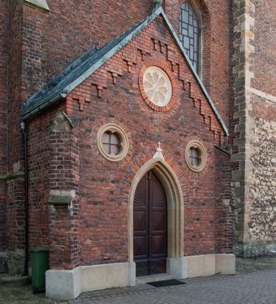 Zdjęcie nr 23: Kościół położony na obszernym placu przylegającym do wschodniej pierzei rynku, na północ od zamku. Plac otoczony ceglanym murem z filarkami. Przed kościołem wydzielony plac, dawny cmentarz, na nim figura św. Jana Kantego. W południowo-wschodnim narożu placu grobowiec księżnej Apolonii Potockiej. Kościół orientowany, halowy, trójnawowy, czteroprzęsłowy, z dwuprzęsłowym zamkniętym wielobocznie prezbiterium. Nawa główna szersza od naw bocznych. Nawy boczne zakończone od wschodu poligonalnymi kaplicami. Od strony północnej do nawy przylega kruchta. W północno-zachodnim narożniku kwadratowa wieża mieszcząca kaplicę w przyziemiu. Do zachodniego przęsła nawy głównej dostawiony głęboki ryzalit z kruchtą w przyziemiu i chórem na piętrze z prospektem organowym. Od północnej strony przylega piętrowa zakrystia, zamknięta wielobocznie. Nawa główna od bocznych oddzielona czworobocznymi filarami o ściętych narożach. Prezbiterium otwarte do korpusu ostrołukową tęczą. W korpusie sklepienie o konstrukcji żelbetowej, stylizowane na gotyckie. W kaplicy pod wieżą sklepienie kolebkowe, w kruchcie zachodniej sufit. Prezbiterium nakryte sklepieniem krzyżowo-żebrowym z żebrami spływającymi na konsole. Wnętrze oświetlają okna ostrołukowe, wypełnione witrażami; dwa w zamknięciu prezbiterium (środkowy otwór zamurowany), dwa na ścianie południowej. Portal z prezbiterium do zakrystii zamknięty łukiem w ośli grzbiet. Otwory drzwiowe prostokątne, różnej wielkości. Kaplica pod wieżą otwarta do wnętrza ostrołukowymi arkadami. Otwory okienne wąskie, prostokątne, ostrołukowe, wypełnione witrażem; cztery w ścianie północnej i południowej, jedno, szersze w ścianie zachodniej nad chórem. Wieża oświetlona małymi, wąskimi oknami zakończonymi łukiem odcinkowym i ostrołukowym. Fasada jednoosiowa, dwukondygnacyjna, zwieńczona szczytem schodkowym z ceglanymi laskami. Niesymetrycznie umieszczone wejście ujęte kamiennym, profilowanym portalem, zamkniętym ostrołukowo. Ponad nim rozglifione ostrołukowe okno. Od północy wieża wbudowana w naroże kościoła, wysunięta nieco przed lico fasady. W dolnej partii kamienna, w górnej ceglana, na rzucie prostokąta, czterokondygnacyjna. Piętro pierwsze i drugie oddzielone kamiennym gzymsem. Trzy dolne kondygnacje gotyckie, czwarta neogotycka (projektu Franciszka Marii Lanciego z 1836 r). Na osi pojedyncze okna. W parterze okno ciosowe, prostokątne, ponad nim wmurowany późnogotycki maswerk ostrołukowy z motywami rybich pęcherzy i psiego zęba, wyżej kartusz z herbem Leliwa. Na pierwszym piętrze okno ostrołukowe z parapetem na konsolkach, w opasce ceglanej zamkniętej ostrołukiem wklęsłym. Drugie piętro, okno ostrołukowe w opasce kamiennej, ponad nim okrągła tarcza zegarowa. Ostatnia kondygnacja ze ściętymi narożami, na których wysunięte przed lico muru krenelażowe wieżyczki zwieńczone kamiennymi szczytami w formie ostrosłupów. Od zachodu masywny łuk półokrągły uformowany z kształtek ceramicznych, w jego polu triforium ostrołukowe. Ponad nim okulus. Pod okapem dachu fryz z ceglanych konsolek oraz gąsiory układane w motyw rybiej łuski. Dach iglicowy. Elewacja południowa. Portal kamienny na cokole, profilowany, ostrołukowy. Archiwolty przechodzące w łuk o formie oślego grzbietu, wsparte na konsolkach zdobionych motywem roślinnym. Skrajna archiwolta z czołgankami zwieńczona pinaklem z kwiatonem. Po bokach analogiczne pinakle; W prezbiterium portal kamienny na cokole, profilowany, ostrołukowy, z dekoracją z motywem skręconego sznura; w kluczu herb Odrowąż, oraz data 1767 i litery LG OH OFP. W ścianę korpusu wmurowane kamienne epitafium ks. Pawła Gabańskiego plebana zatorskiego (zm. 1825), nad nim kartusz z herbem Łodzia.Trzy okna analogiczne jak w fasadzie, i jedno o połowę węższe. Elewacja północna. Kruchta ceglana, na cokole, opięta przyporami. Na osi portal kamienny, profilowany, ostrołukowy. Ponad nim kamienna rozeta z monogramem Marii, po bokach dwa okna o wykroju czworoliścia w okrągłych, kamiennych opaskach. Od strony północno-zachodniej zakrystia na rzucie prostokąta, zamknięta wielobocznie, piętrowa, w dolnej części kamienna (pozostałość pierwotnego kościoła), wyżej ceglana (piętro dobudowane 1915 r.). Od północy portal w opasce ceglanej, zamknięty łukiem odcinkowym. Ponad nim ostrołukowe, ceglane okno. Dwa okna analogiczne jak w fasadzie i jedno o połowę węższe. Kościół opięty przyporami, na wysokości ław okiennych gzyms kapnikowy wyłamany nad portalem północnym. Przypory z kapnikami w zwieńczeniu i na 2/3 wysokości. Pod dachem gzyms konsolkowy. Dach dwuspadowy, sygnaturka wieloboczna z ostrołukowymi prześwitami, zwieńczona hełmem iglicowym.