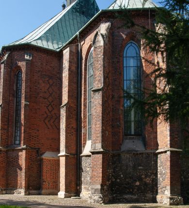 Zdjęcie nr 32: Kościół położony na obszernym placu przylegającym do wschodniej pierzei rynku, na północ od zamku. Plac otoczony ceglanym murem z filarkami. Przed kościołem wydzielony plac, dawny cmentarz, na nim figura św. Jana Kantego. W południowo-wschodnim narożu placu grobowiec księżnej Apolonii Potockiej. Kościół orientowany, halowy, trójnawowy, czteroprzęsłowy, z dwuprzęsłowym zamkniętym wielobocznie prezbiterium. Nawa główna szersza od naw bocznych. Nawy boczne zakończone od wschodu poligonalnymi kaplicami. Od strony północnej do nawy przylega kruchta. W północno-zachodnim narożniku kwadratowa wieża mieszcząca kaplicę w przyziemiu. Do zachodniego przęsła nawy głównej dostawiony głęboki ryzalit z kruchtą w przyziemiu i chórem na piętrze z prospektem organowym. Od północnej strony przylega piętrowa zakrystia, zamknięta wielobocznie. Nawa główna od bocznych oddzielona czworobocznymi filarami o ściętych narożach. Prezbiterium otwarte do korpusu ostrołukową tęczą. W korpusie sklepienie o konstrukcji żelbetowej, stylizowane na gotyckie. W kaplicy pod wieżą sklepienie kolebkowe, w kruchcie zachodniej sufit. Prezbiterium nakryte sklepieniem krzyżowo-żebrowym z żebrami spływającymi na konsole. Wnętrze oświetlają okna ostrołukowe, wypełnione witrażami; dwa w zamknięciu prezbiterium (środkowy otwór zamurowany), dwa na ścianie południowej. Portal z prezbiterium do zakrystii zamknięty łukiem w ośli grzbiet. Otwory drzwiowe prostokątne, różnej wielkości. Kaplica pod wieżą otwarta do wnętrza ostrołukowymi arkadami. Otwory okienne wąskie, prostokątne, ostrołukowe, wypełnione witrażem; cztery w ścianie północnej i południowej, jedno, szersze w ścianie zachodniej nad chórem. Wieża oświetlona małymi, wąskimi oknami zakończonymi łukiem odcinkowym i ostrołukowym. Fasada jednoosiowa, dwukondygnacyjna, zwieńczona szczytem schodkowym z ceglanymi laskami. Niesymetrycznie umieszczone wejście ujęte kamiennym, profilowanym portalem, zamkniętym ostrołukowo. Ponad nim rozglifione ostrołukowe okno. Od północy wieża wbudowana w naroże kościoła, wysunięta nieco przed lico fasady. W dolnej partii kamienna, w górnej ceglana, na rzucie prostokąta, czterokondygnacyjna. Piętro pierwsze i drugie oddzielone kamiennym gzymsem. Trzy dolne kondygnacje gotyckie, czwarta neogotycka (projektu Franciszka Marii Lanciego z 1836 r). Na osi pojedyncze okna. W parterze okno ciosowe, prostokątne, ponad nim wmurowany późnogotycki maswerk ostrołukowy z motywami rybich pęcherzy i psiego zęba, wyżej kartusz z herbem Leliwa. Na pierwszym piętrze okno ostrołukowe z parapetem na konsolkach, w opasce ceglanej zamkniętej ostrołukiem wklęsłym. Drugie piętro, okno ostrołukowe w opasce kamiennej, ponad nim okrągła tarcza zegarowa. Ostatnia kondygnacja ze ściętymi narożami, na których wysunięte przed lico muru krenelażowe wieżyczki zwieńczone kamiennymi szczytami w formie ostrosłupów. Od zachodu masywny łuk półokrągły uformowany z kształtek ceramicznych, w jego polu triforium ostrołukowe. Ponad nim okulus. Pod okapem dachu fryz z ceglanych konsolek oraz gąsiory układane w motyw rybiej łuski. Dach iglicowy. Elewacja południowa. Portal kamienny na cokole, profilowany, ostrołukowy. Archiwolty przechodzące w łuk o formie oślego grzbietu, wsparte na konsolkach zdobionych motywem roślinnym. Skrajna archiwolta z czołgankami zwieńczona pinaklem z kwiatonem. Po bokach analogiczne pinakle; W prezbiterium portal kamienny na cokole, profilowany, ostrołukowy, z dekoracją z motywem skręconego sznura; w kluczu herb Odrowąż, oraz data 1767 i litery LG OH OFP. W ścianę korpusu wmurowane kamienne epitafium ks. Pawła Gabańskiego plebana zatorskiego (zm. 1825), nad nim kartusz z herbem Łodzia.Trzy okna analogiczne jak w fasadzie, i jedno o połowę węższe. Elewacja północna. Kruchta ceglana, na cokole, opięta przyporami. Na osi portal kamienny, profilowany, ostrołukowy. Ponad nim kamienna rozeta z monogramem Marii, po bokach dwa okna o wykroju czworoliścia w okrągłych, kamiennych opaskach. Od strony północno-zachodniej zakrystia na rzucie prostokąta, zamknięta wielobocznie, piętrowa, w dolnej części kamienna (pozostałość pierwotnego kościoła), wyżej ceglana (piętro dobudowane 1915 r.). Od północy portal w opasce ceglanej, zamknięty łukiem odcinkowym. Ponad nim ostrołukowe, ceglane okno. Dwa okna analogiczne jak w fasadzie i jedno o połowę węższe. Kościół opięty przyporami, na wysokości ław okiennych gzyms kapnikowy wyłamany nad portalem północnym. Przypory z kapnikami w zwieńczeniu i na 2/3 wysokości. Pod dachem gzyms konsolkowy. Dach dwuspadowy, sygnaturka wieloboczna z ostrołukowymi prześwitami, zwieńczona hełmem iglicowym.